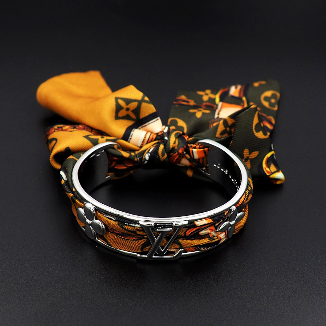 驴家新款LVInitiales Silk 手镯凝聚金属的闪耀光泽与丝带的华美质感，为精雕细琢的圈环融入M