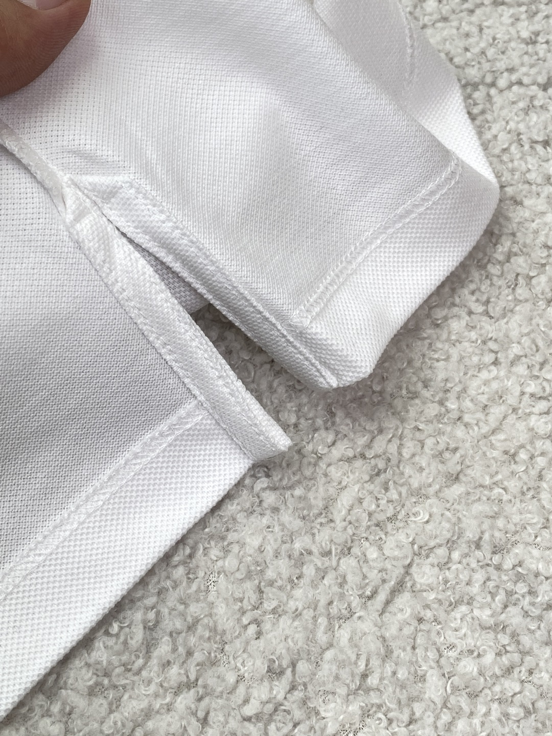 • 面料与工艺：采用棉质珠地布（Cotton Piqué）制作，透气亲肤；罗纹翻领与袖口，搭配珍珠母贝纽