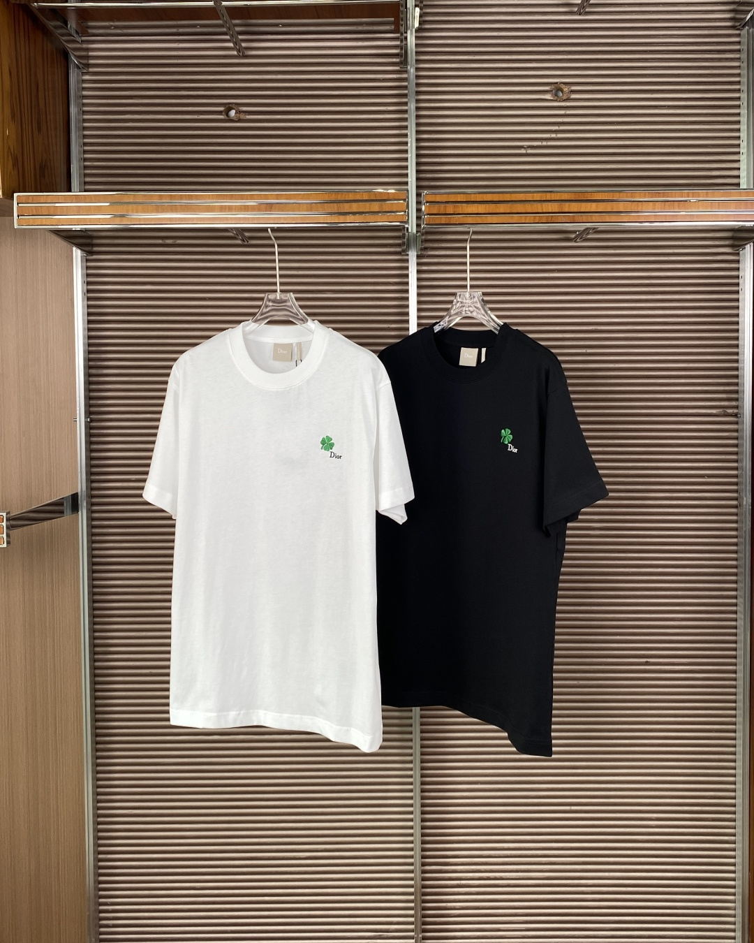 NO:955655,Dior Clover Four-leaf Clover Embroidered Round Neck T-shirt. The iconic embroidered chest is embroidered with a green four-leaf clover (Dior Clover) and the word 'Dior'. The four-leaf clover is Dior's classic lucky symbol, symbolizing good luck and good wishes. The craft material is made of worsted cotton jersey fabric, with a ribbed round neck design, which is both comfortable and stiff.  The style is positioned as minimalist and low-key luxury, abandoning exaggerated large logos, and using delicate embroidery to reflect a sense of luxury, which is suitable for daily casual or smart casual wear. The style is positioned as a loose and casual unisex version, the same style for men and women, suitable for daily commuting and casual wear, and can also be used as an inner wear to create a layered look. 1. The collar label is embroidered with the word 'Dior', the font is clear and regular, and the edges are not off-line. 2.  The embroidered four-leaf clover has fine embroidery stitches, distinct layers of leaves, even spacing between 'Dior' letters, and no jumpers or rough edges. 3. The fabric is made of high-count combed cotton, which is soft to the touch and has a drapey feel, and is not too thin and translucent.,, dior, dior, tees, t-shirt,19860909Dior Clover 四叶草刺绣圆领T恤 标志性刺绣胸前绣有绿色四叶草（Dior Clover）与“Dior”字样,四叶草是迪奥的经典幸运符号,象征好运与美好祝愿. 工艺材质采用精纺棉质平纹针织面料,罗纹圆领设计,兼具舒适感与挺括版型. 风格定位极简低调的奢华感,摒弃夸张大Logo,以细腻刺绣体现高级感,适合日常休闲或Smart Casual穿搭. 版型定位宽松休闲的中性版型,男女同款,适合日常通勤、休闲穿搭,也可作为内搭打造层次感造型. 1. 领标领标为刺绣“Dior”字样,字体清晰规整,边缘无脱线. 2. 刺绣四叶草刺绣针脚细密,叶片层次分明,“Dior”字母间距均匀,无跳线、毛边. 3. 面料面料为高支精梳棉,触感柔软且有垂坠感,不会过于轻薄透肤.,,dior,dior,tees，t-shirt,,Women's clothing