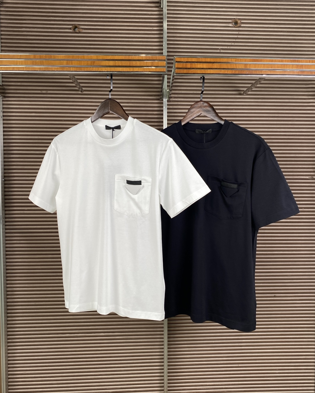 NO:842506,(Liquid ammonia mercerized fabric) Prada triangle pocket short-sleeved T-shirt. The brand logo is sewn with Prada's iconic triangle patch on the left breast pocket. This is a highly recognizable detail of the brand. The design is classic round neck short sleeves, slightly loose/square cut, and straight hem, taking into account both comfort and neatness. Fabric and ingredients Cotton, the fabric is high-count plain cotton, smooth and breathable, and good skin-friendly.  The silhouette has a slightly loose shoulder-drop effect at the back, which is not flattering and can modify the body shape. The pocket triangle mark becomes the visual focus, low-key and recognizable. Wearing scene: daily casual wear with jeans/casual pants + white shoes/sneakers to create a minimalist and high-end feel. Wear a light business suit jacket with this T-shirt inside to balance formality and relaxation. Black and white can be used as a couple's style, with unified style and different details.  Care instructions: Wash inside out with cold water, do not wring out, do not dry clean, cover the cloth surface when ironing to protect the triangle mark and fabric texture.,, prada, prada, jeans, jackets & coats, T-shirt, tees, t-shirt, business suit,19860909（液氨丝光面料） Prada（普拉达） 三角标口袋短袖T恤 品牌标识左胸口袋处缝制有Prada标志性三角标饰片.这是品牌辨识度极高的细节. 版型设计经典圆领短袖,版型偏微宽松/方正剪裁,直裁下摆,兼顾舒适感与利落感. 面料与成分棉,面料为高支平纹棉,触感顺滑透气,亲肤性佳. 版型呈现上身后为微宽松落肩效果,不挑身材,能修饰身形,口袋三角标成为视觉焦点,低调又有辨识度. 穿搭场景 日常休闲搭配牛仔裤/休闲裤+小白鞋/板鞋,打造极简高级感. 轻商务外搭西装外套,内搭这件T恤,平衡正式与松弛感. 情侣穿搭黑白两色可作为情侣款,风格统一又有细节差异. 护理说明需冷水反面清洗、不可拧干、不可干洗,熨烫时需覆盖布面,以保护三角标与面料质感.,,prada,prada,jeans,jackets & coats,T-shirt,tees，t-shirt,business suit,,Women's clothing