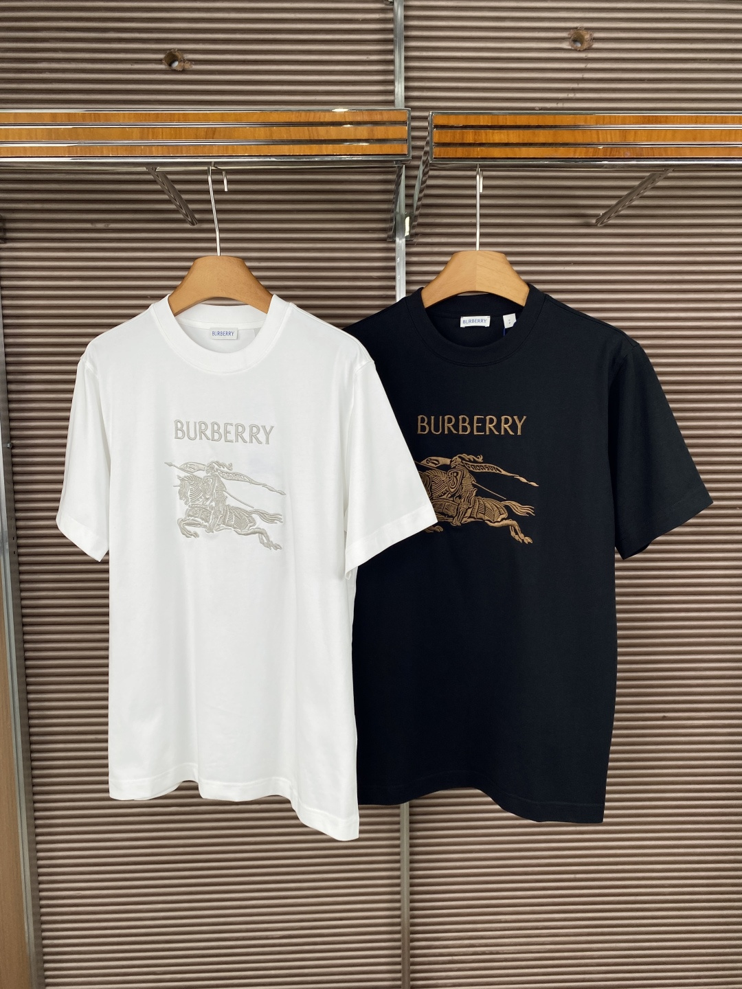 NO:835087,Burberry Equestrian Rider Embroidered Short Sleeve T-shirt. The iconic elements are heavily embroidered on the front with the same color/contrast color, showing the brand's classic Equestrian Rider logo and the word 'BURBERRY', which is one of the most recognizable symbols of the brand. The fit and fabric are loose round-neck cut, and the fabric is cotton, high-count jersey material, skin-friendly and breathable, suitable for daily wear.  The color selection provides two classic colors: white (light gray embroidery) and black (bronze embroidery), suitable for different dressing styles. The detailed craftsmanship neckline is reinforced rib design, which is not easy to deform; the embroidery craftsmanship is exquisite and the lines are clear, which enhances the overall texture. Daily casual wear with jeans/casual pants is simple and refreshing, suitable for spring and summer. Layer the style with a shirt or knitted cardigan to create a layered look, suitable for commuting or light business scenes.  The style adapts to the white model for a more clean and youthful look, and the black model for a more calm and high-end look.,,burberry,jeans,shirts,T-shirt,tees,t-shirt,19860909Burberry 马术骑士刺绣短袖T恤 标志性元素正面采用同色系/对比色重工刺绣,呈现品牌经典的马术骑士徽标与「BURBERRY」字样,是品牌辨识度最高的符号之一. 版型与面料宽松圆领剪裁,面料为棉,高支平纹针织材质,亲肤透气,适合日常穿着. 配色选择提供白色（浅灰刺绣）与黑色（古铜色刺绣）两种经典配色,适配不同穿搭风格. 细节工艺领口为加固罗纹设计,不易变形；刺绣工艺精致,线条清晰,提升整体质感.  日常休闲搭配牛仔裤/休闲裤,简约清爽,适合春夏季节. 叠穿造型外搭衬衫或针织开衫,营造层次穿搭,适配通勤或轻商务场景. 风格适配白色款更显干净少年感,黑色款更具沉稳高级感.,,burberry,jeans,shirts,T-shirt,tees，t-shirt,,Women's clothing