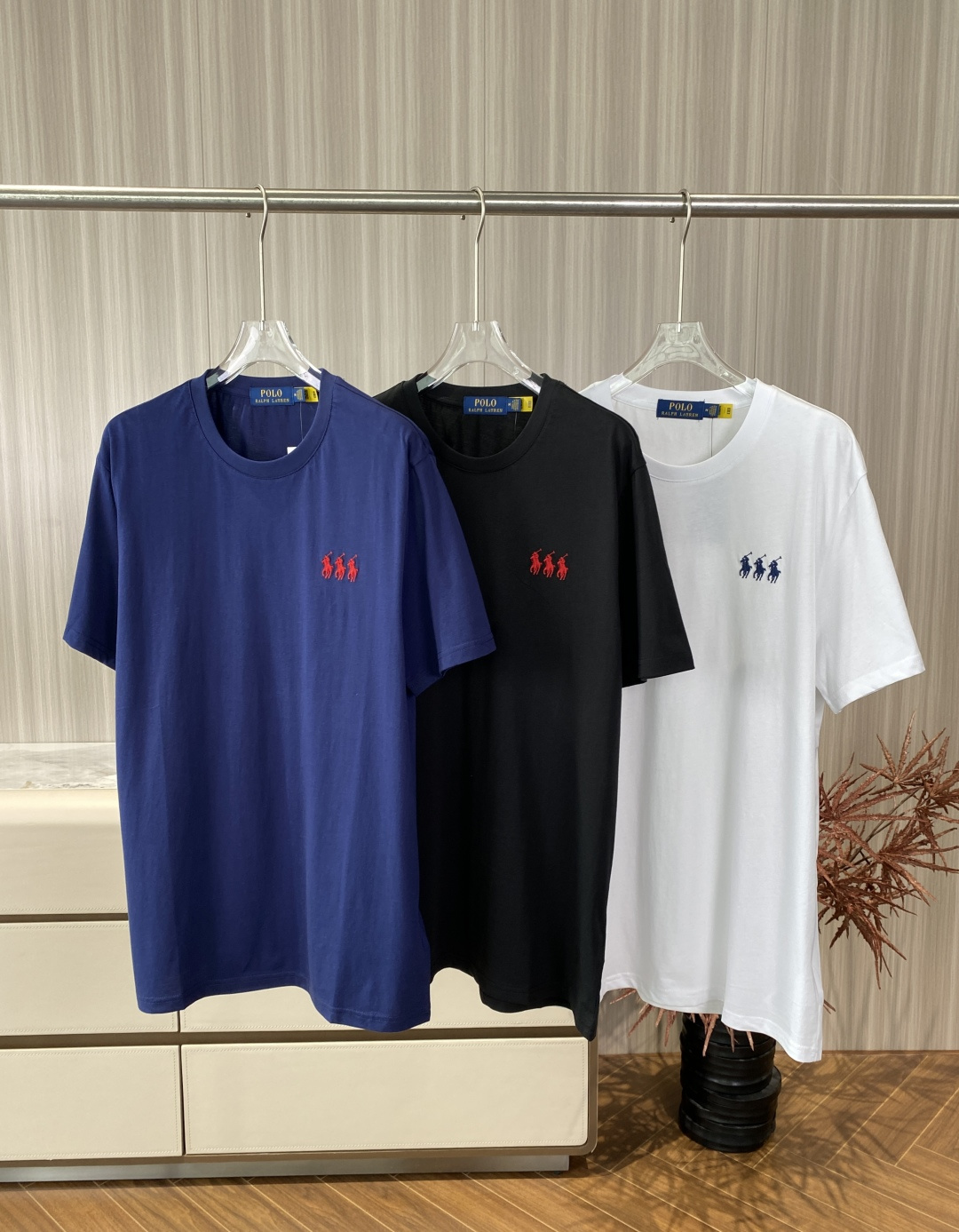 NO:903722,Polo Ralph Lauren three-horse embroidered horse logo casual round neck short-sleeved T. Fabric: Combed cotton, pre-washed and pre-shrunk, soft to the touch, good drape, not easy to deform. Summer fabric, breathable and not stuffy, while ensuring a crisp fit. The version is classic Regular Fit, not tight nor too loose, suitable for most body types.  The round neck is hemmed with double-layer ribbing, which is durable and not easy to deform; the cuffs and hem are hemmed with double needles, and the workmanship is solid. Embroidery technology: The three-horse embroidery on the left chest is high-density three-dimensional embroidery, with fine stitches and uniform colors (the white model is navy embroidery, the navy/black model is red embroidery). The embroidery edges are flat, without skipping or threading. Color selection: White is the most classic, refreshing and clean, suitable for spring and summer, and goes well with jeans and khaki pants.  Navy blue has a stronger American retro feel, is white and stain-resistant, and is suitable for commuting and college-style wear. Black is versatile and slimming, suitable for layering in autumn and winter, and can also be used as a basic inner wear. Wearing scenarios: Daily casual wear alone with straight jeans and white shoes, a typical American preppy style. Wear it with a casual suit or denim jacket for commuting, and match the bottoms with casual trousers, which is simple and decent.  Wear it layered under a hooded sweatshirt or cardigan to expose the collar and hem to add a sense of layering.,,loro piana,hoodie,sweatshirts,jeans,jackets & coats,T-shirt,business suit,hats,19860909Polo Ralph Lauren 三匹刺绣马标休闲圆领短袖T 面料 精梳棉（Combed Cotton）,经过预水洗和预缩处理,手感柔软、垂坠感好,不易变形. 夏季面料,透气不闷热,同时能保证版型挺括. 版型 经典Regular Fit（常规合身版）,不紧绷也不过于宽松,适配大多数身材. 圆领采用双层罗纹包边,耐穿不易变形；袖口和下摆采用双针锁边,做工扎实. 刺绣工艺 左胸三匹马刺绣为高密度立体刺绣,针脚细密,颜色均匀（白色款为藏青刺绣,藏青/黑色款为红色刺绣）. 刺绣边缘平整,无跳线、脱线. 配色选择 白色最经典,清爽干净,适合春夏,搭配牛仔裤、卡其裤都很和谐. 藏青色美式复古感更强,显白且耐脏,适合通勤、学院风穿搭. 黑色百搭显瘦,适合秋冬叠穿,也可作为基础内搭. 穿搭场景 日常休闲单穿搭配直筒牛仔裤+小白鞋,典型美式Preppy风. 通勤外搭休闲西装或牛仔外套,下装搭配休闲西裤,简约得体. 叠穿内搭在连帽卫衣或开衫里,露出领口和下摆,增加层次感.,,loro piana,hoodie,sweatshirts,jeans,jackets & coats,T-shirt,business suit,hats,,Women's clothing