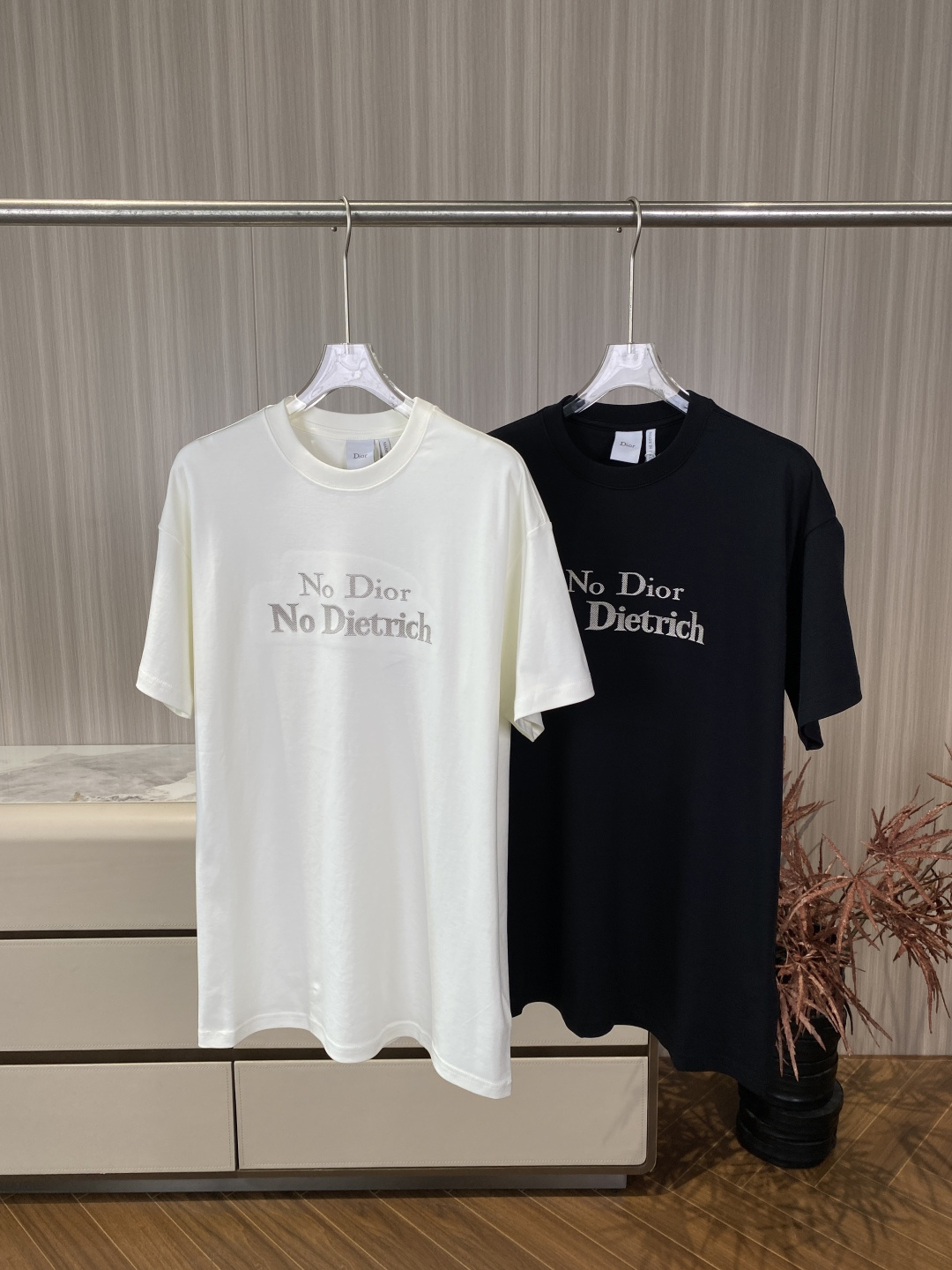 NO:834357,(Original customization) Real praise Dior 2026 Spring and Summer Round Neck Embroidered Short-Sleeved T-shirt The loose-shouldered (Oversized) round neck version optimizes the shoulder line ratio, adapts to diverse body types, and creates a lazy and casual visual effect. The neckline technology ribbed round neck uses double-needle hemming technology to fit the neck curve and is not easy to loosen and deform after long-term washing, ensuring wearing comfort and durability. The embroidery process uses high-density flat embroidery technology on the front of the body, and 'No'  'Dior No Dietrich' is embroidered with retro serif fonts, the stitches are delicate and full, and the letters are clearly layered; the off-white model is embroidered in the same color, low-key and refined; the black model is embroidered in contrasting colors, with stronger visual tension. The details are embellished with dropped shoulders, and the cuffs and hem are double-needle flat seams, and the overall lines are neat and simple. Material and origin information  The fabric is made of combed cotton (jersey knitted fabric), which is both stiff and skin-friendly and breathable. It absorbs moisture and perspiration, and is not easily deformed after long-term wear. It is suitable for spring and summer wear. The embroidery decorative embroidery thread is rayon, which has a strong luster and enhances the sophistication. The embroidery process has dense stitches, smooth edges of letters without jumpers, and accurate font proportions; imitation embroidery is blurred, has many rough edges, and the fonts are deformed.  The 'Dior' font on the collar label and tag collar label is clear, and the edges are neatly seamed. The texture of the fabric is fine and soft, with a natural drape. Wearing and maintenance suggestions Wearing inspiration Pair it with straight jeans and white shoes for daily casual wear to create a relaxed street look. For casual commuting, pair it with suit trousers and loafers to create a smart casual business style. Wear it layered with a white turtleneck base and a denim jacket or windbreaker, suitable for transitional wear in spring and autumn.  Washing and care instructions: Hand wash in cold water or gentle machine wash, use neutral detergent, do not bleach. Lay flat to dry to avoid hanging and causing deformation of the garment. Do not expose to the sun. Iron with low-temperature steam, iron on the reverse side to protect the embroidery process., dior, dior, versace, loafers, jeans, jackets & coats, T-shirt, tees, t-shirt, business suit,19860909（原版定制）实物赞 Dior迪奥2026春夏圆领刺绣短袖T恤 版型剪裁宽松落肩（Oversized）圆领版型,优化肩线比例,适配多元身材,营造慵懒随性的视觉效果. 领口工艺罗纹圆领采用双针包边工艺,贴合颈部曲线,久洗不易松垮变形,保证穿着舒适度与耐用性. 刺绣工艺衣身正面采用高密平绣工艺,将「No Dior No Dietrich」以复古衬线字体绣制,针脚细腻饱满,字母层次分明；米白色款为同色刺绣,低调精致；黑色款为对比色刺绣,视觉张力更强. 细节点缀肩部采用落肩剪裁,袖口与下摆为双针平缝,整体线条利落简洁. 材质与产地信息 面料成分精梳棉（平纹针织面料）,兼具挺括感与亲肤透气性,吸湿排汗,久穿不易变形,适合春夏季节穿着. 刺绣装饰刺绣线为人造丝,光泽感强,提升精致度.  刺绣工艺刺绣针脚密实,字母边缘平整无跳线,字体比例精准；仿品刺绣模糊、毛边多,字体变形. 领标与吊牌领标「Dior」字体清晰,边缘锁边工整. 面料质感精梳棉面料细腻柔软,有自然垂感. 穿搭与保养建议 穿搭灵感 日常休闲搭配直筒牛仔裤、小白鞋,营造松弛感街头造型. 通勤轻熟搭配西装裤、乐福鞋,打造Smart Casual商务休闲风格. 叠穿搭配内搭白色高领打底,外搭牛仔外套或风衣,适合春秋季节过渡穿搭. 洗护规范 洗涤冷水手洗或轻柔机洗,使用中性洗涤剂,不可漂白. 晾晒平铺晾干,避免悬挂导致衣身变形,不可暴晒. 熨烫低温蒸汽熨烫,需反面熨烫以保护刺绣工艺.,,dior,dior,versace,loafers,jeans,jackets & coats,T-shirt,tees，t-shirt,business suit,,Women's clothing