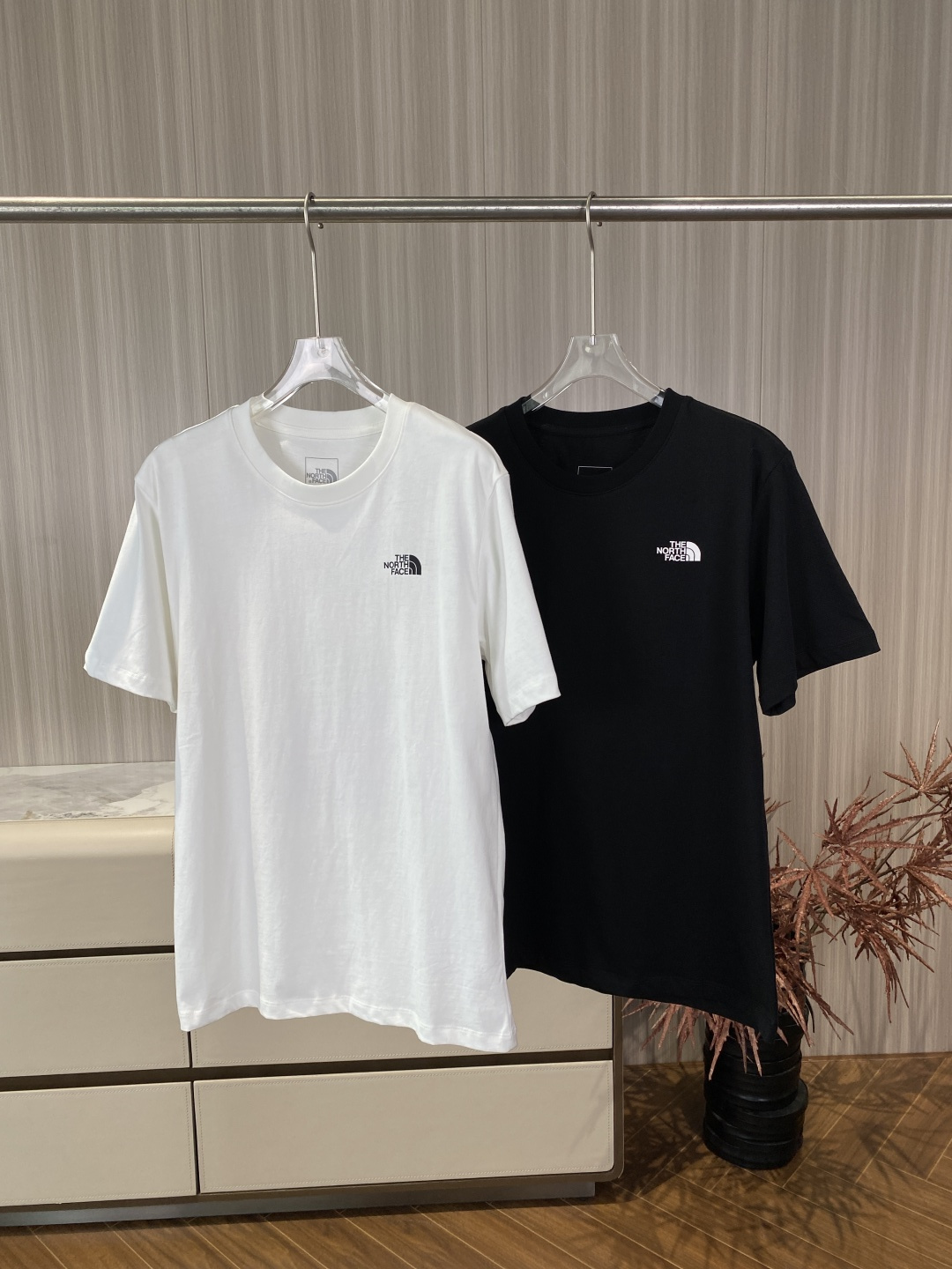 NO:827842,The North Face's classic pure cotton short-sleeved T-shirt. The neckline has a classic round neck design. It is made of high-density threaded fabric, which is elastic and not easy to deform, and will not loosen easily after long-term wear. The regular straight version is not flattering on the figure, and the upper body is comfortable and not tight, taking into account daily commuting and light outdoor scenes. The logo is printed with a white/black 'The North Face' brand logo and the iconic snow mountain graphic on the left chest, which is low-key and unobtrusive, in line with the brand's minimalist outdoor style.  The double-needle overlocking process on the cuffs ensures neat routing to prevent curling and improve wearability. Letter printing on the front maintains a simple and low-key visual effect. Large contrasting artistic printing on the back, the core elements include the brand logo and the words 'THE NORTH FACE' in the upper left corner. The classic outdoor tent line pattern in the upper right corner echoes the brand's outdoor genes. The brand slogan 'NEVER STOP EXPLORING' in the middle conveys the spirit of exploration.  The lower part has a hand-painted snow mountain pattern, with geometric textures and flying bird elements, and the color is lively. Color differences: The white model has contrasting colors of pink + green + black, fresh and lively, and looks more youthful. The black model has contrasting colors of blue + green + white, which has a calm and cool feel and is easier to match. The fabric is combed pure cotton (labeled 'COTTON'), medium thickness, breathable and sweat-absorbent, skin-friendly and not stuffy, suitable for spring and summer wear, and can also be used as an inner layer for autumn and winter.  The basic model for daily commuting is worn alone + casual pants/jeans, simple and clean; the printed model is paired with overalls/sports pants to create a street trend. For outdoor travel, it is breathable and sweat-absorbent as a basic layer for hiking and camping. It is also very coordinated with a jacket or sun protection clothing. For couples, black and white + the same style with different color prints can be combined into a couple style, with visual echo and differentiation.  Inner wear scene In autumn and winter, it can be used as an inner wear for sweaters and jackets, revealing the collar and small logo to increase the sense of layering.,, The North Face, hoodie, sweatshirts, jeans, jackets & coats, T-shirt, tees, t-shirt,19860909北面（The North Face）经典款纯棉短袖T恤 领口经典圆领设计,采用高密度螺纹面料,弹性好且不易变形,久穿不易松垮. 版型常规直筒版型,不挑身材,上身舒适不紧绷,兼顾日常通勤与轻度户外场景. Logo左胸位置印有白色/黑色的“The North Face”品牌Logo及标志性雪山图形,低调不张扬,符合品牌极简户外风格. 袖口双针锁边工艺,走线工整,防止卷边,提升耐穿度.  正面字母印花,保持简约低调的视觉效果. 背面大幅撞色艺术印花,核心元素包括 左上角品牌Logo与“THE NORTH FACE”字样. 右上角经典户外帐篷线条图案,呼应品牌户外基因. 中部“NEVER STOP EXPLORING”品牌标语,传递探索精神. 下部手绘风格雪山图案,搭配几何纹理与飞鸟元素,色彩活泼. 配色差异 白色款粉+绿+黑撞色,清新活泼,更显年轻. 黑色款蓝+绿+白撞色,沉稳酷感,更易搭配. 面料精梳纯棉（标签标注“ COTTON”）,中等厚度,透气吸汗,亲肤不闷,适合春夏季节穿着,也可作为秋冬内搭. 日常通勤基础款单穿+休闲裤/牛仔裤,简约干净；印花款搭配工装裤/运动束脚裤,打造街头潮流感. 户外出行作为徒步、露营的基础层,透气吸汗,搭配冲锋衣或防晒衣也十分协调. 情侣穿搭黑白双色+同款不同色印花,可组成情侣款,视觉呼应又有区分度. 内搭场景秋冬季节可作为卫衣、夹克的内搭,露出领口与小Logo,增加层次感.,,The North Face,hoodie,sweatshirts,jeans,jackets & coats,T-shirt,tees，t-shirt,,Women's clothing