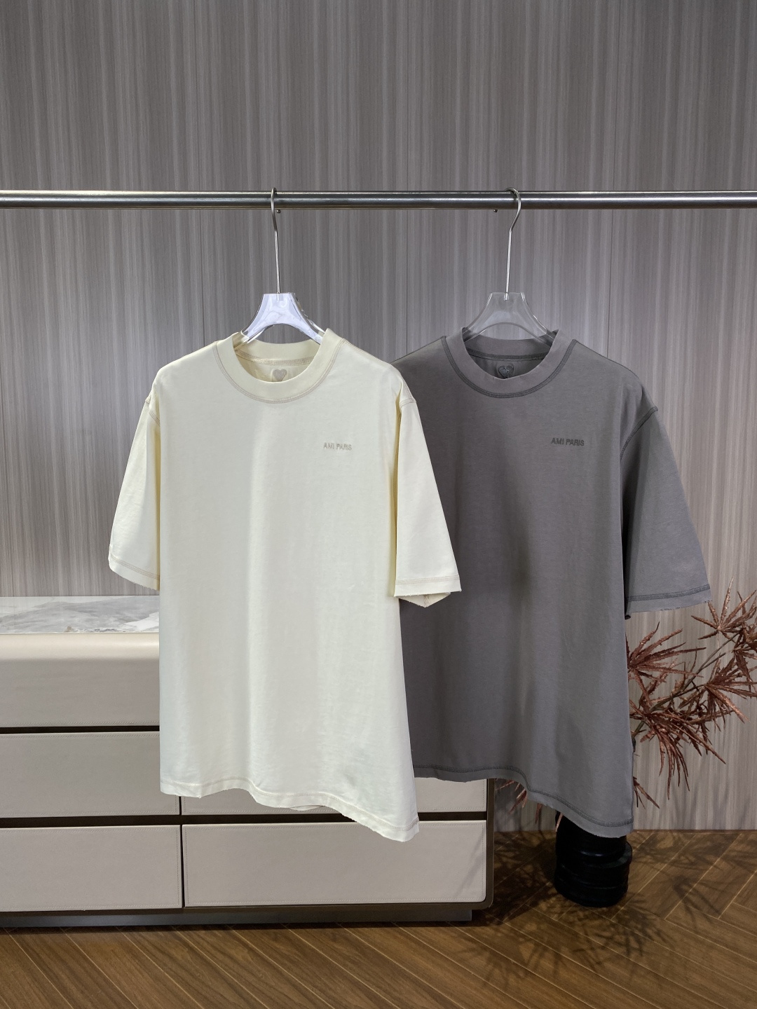 NO:873365,AMI PARIS same-color embroidered love heart round-neck short-sleeved T-shirt 1. Minimalist logo embroidery. The left chest is embroidered with the words 'AMI PARIS' using the same color embroidery process. The font is slim and neat, low-key and unobtrusive, in line with the brand's minimalist tone. The brand's iconic love A (Ami de Cur) is embroidered on the back of the neck, also embroidered with the same color thread, with fine stitching. 2. Retro distressed technology  The collar, cuffs, and hem are all processed with raw edges to simulate the natural wear and tear effect, giving it a retro workwear feel. The seams of the entire garment are decorated with topstitching of the same color to enhance the outline and make the basic style more detailed. 3. Loose fit, oversize off-shoulder tailoring, longer length, suitable for various body types, creating a casual and lazy French casual feel. The material is a large body fabric.  Cotton, soft and skin-friendly, has good breathability, is a heavy cotton material, has a strong drape and is not easy to deform. The color selection is off-white, gentle and fresh, suitable for spring and summer, and looks cleaner when paired with light-colored bottoms. Gray is calm and advanced, with a distressed texture, suitable for cool casual or commuting styles. Wearing scene: French casual off-white + light blue straight jeans + white shoes, refreshing and clean. Cool street gray + black overalls +  Martin boots, low-key and textured. Pair them with a white high-collar base and a denim jacket/leather jacket for a layered look, suitable for the transitional season between spring and autumn. Pair the lazy style with wide-leg linen pants to create a casual and relaxed French atmosphere.,,versace,boots,jeans,jackets & coats,T-shirt,tees,t-shirt,leather jacket,19860909AMI PARIS 同色刺绣爱心圆领短袖T恤 1. 极简标识刺绣 左胸位置采用同色刺绣工艺绣有「AMI PARIS」字样,字体纤细工整,低调不张扬,符合品牌极简调性. 后颈处绣有品牌标志性的爱心A（Ami de Cur）,同样为同色线刺绣,针脚细密. 2. 复古做旧工艺 领口、袖口、下摆均采用毛边磨边处理,模拟自然穿着磨损效果,自带复古工装感. 全衣缝线采用同色明线装饰,强化轮廓感,让基础款更具细节层次. 3. 宽松版型 Oversize落肩剪裁,衣长偏长,适配各种身材,打造随性慵懒的法式休闲感. 材质大身面料为 棉,手感柔软亲肤,透气性佳,属于重磅棉材质,垂坠感强不易变形. 配色选择 米白色温柔清新,适合春夏,搭配浅色系下装更显干净. 灰色沉稳高级,自带做旧质感,适配酷感休闲或通勤造型. 穿搭场景 法式休闲米白色款 + 浅蓝直筒牛仔裤 + 小白鞋,清爽干净. 酷感街头灰色款 + 黑色工装裤 + 马丁靴,低调有质感. 叠穿造型内搭白色高领打底,外穿牛仔夹克/皮衣,适配春秋过渡季. 慵懒风搭配阔腿亚麻裤,打造随性松弛的法式氛围感.,,versace,boots,jeans,jackets & coats,T-shirt,tees，t-shirt,leather jacket,,Women's clothing