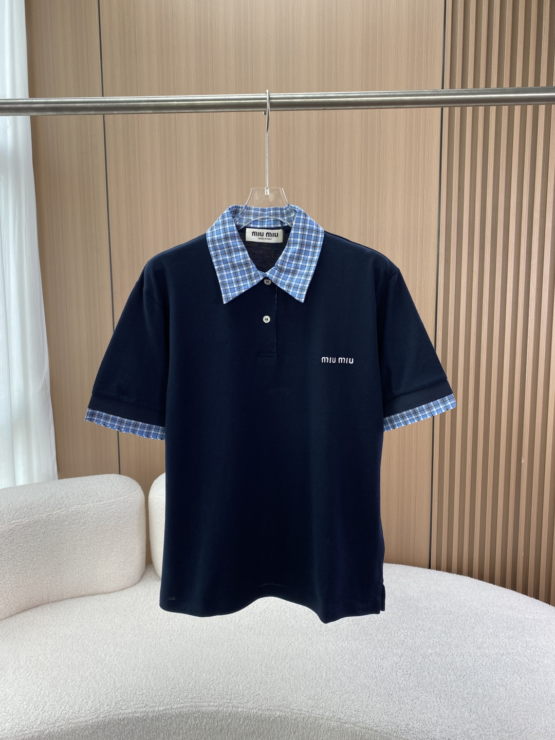 NO:861914,Miu Miu/Miu Miu Women's dark blue with light blue plaid trim short-sleeved Polo shirt Design details The dark blue main body with plaid elements is decorated with light blue plaid on the collar and cuffs. The classic plaid element is injected into the retro college style. The color matching is harmonious and layered, highlighting the brand's unique aesthetics. The lapels are designed with neat lapels to modify the neck line and add a capable temperament while retaining the sporty and casual feel of the Polo shirt. It can be worn alone or paired with a jacket to create a variety of styles. The brand logo has a delicate 'Miu' on the chest  Miu' embroidered logo, low-key to highlight the brand identity, enhance the recognition and sophistication of clothing. Cutting style: short-sleeved straight fit, tolerant to the body, comfortable and comfortable to wear, short design can visually optimize body proportions, show vitality and playfulness. Outfit suggestions  It can be paired with pleated skirts from the same brand to create a unified college-style look; it can also be paired with simple jeans to create a casual and casual atmosphere; it can be worn with a knitted cardigan or a small suit to suit more occasions.,,miumiu,skirts,jeans,jackets & coats,T-shirt,business suit,19860909Miu Miu/缪缪 女士深蓝拼浅蓝格纹边饰短袖Polo衫 设计细节 格纹元素深蓝主体搭配浅蓝格纹装饰领口与袖口,经典格纹元素注入复古学院风,色彩搭配和谐又具层次感,彰显品牌独特美学 . 翻领设计利落的翻领,修饰颈部线条,增添干练气质,同时保留Polo衫的运动休闲感,可单穿或搭配外套打造多样风格 . 品牌标识胸口精致的“Miu Miu”刺绣徽标,低调彰显品牌身份,提升服装辨识度与精致度 . 版型剪裁 短袖直筒版型,对身材包容性强,穿着舒适自在,短款设计能在视觉上优化身材比例,展现活力俏皮 . 穿搭建议 可搭配同品牌百褶短裙,打造统一学院风造型；也能与简约牛仔裤相配,营造休闲随性氛围；外搭针织开衫或小西装,适配更多场合.,,miumiu,skirts,jeans,jackets & coats,T-shirt,business suit,,Women's clothing