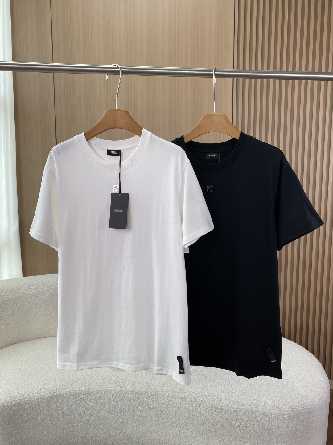 NO:912030,FENDI Fendi metal FF buckle round neck T-shirt. The color and design are classic black and white. The chest uses three-dimensional metal FF hidden buttons (classic elements of Fendi Logo). Compared with large prints, it is more low-key and advanced, suitable for business casual and daily commuting. The fabric parameters are high-count cotton, skin-friendly and breathable; judging from the physical texture of the same style, it is stiff and not easy to deform, and the drape is better than ordinary cotton T-shirts. 2. Craftsmanship details  The neckline adopts a double-layer rib reinforcement design, which is not easy to loosen and deform after long-term wear, and the neckline has excellent rebound rate. The hardware metal FF buckle has a matte frosted texture, with rounded edges, no sharp burrs, a firm buckle and is not easy to oxidize and paint off. The side seams of the line-cut body are made of flat hemming technology without excess threads, reflecting the rigorous workmanship of the luxury brand. 1. Business casual style (workplace/light social) Pair with a navy blue/dark gray suit jacket +  Dark gray trousers/slim casual trousers. Highlighted metal buckles serve as details to break up the dullness of formal attire and are suitable for business meetings and informal meetings. Shoes include loafers and simple leather sneakers. 2. Urban cool style (daily outings/dating). Pair with black ripped jeans + black functional belt + Martin boots/white shoes. Highlights: black and white contrasting colors have strong visual impact, suitable for young people, highlighting unobtrusive taste.  Accessories are paired with a simple metal watch, echoing the FF buckle on the chest, to enhance the overall sophistication. 3. Minimalist home/light sports wear with gray leggings + slippers/sneakers. Highlighted cotton fabric is breathable and sweat-absorbent, and the loose fit is suitable for light scenes such as home and walking.,,fendi,fendi,loafers,boots,sneakers,slippers,jeans,jackets & coats,tees,t-shirt,business suit,19860909FENDI芬迪金属FF扣圆领T恤 配色与设计经典黑与白色,胸前采用立体金属FF暗扣（Fendi Logo经典元素）,相比大印花更低调高级,适合商务休闲与日常通勤. 面料参数高支棉,亲肤透气；从同款实物质感看,挺括不易变形,垂坠感优于普通纯棉T恤. 2. 工艺细节 领口采用双层罗纹加固设计,久穿不易松垮变形,领口回弹率极佳. 五金金属FF扣为哑光磨砂质感,边缘打磨圆润,无尖锐毛刺,扣合牢固且不易氧化掉漆. 走线衣身侧缝采用平整包边工艺,无多余线头,体现奢品品牌的严谨做工. 1. 商务休闲风（职场/轻社交） 搭配外搭藏青色/深灰色西装外套 + 深灰色西裤/修身休闲裤. 亮点金属扣作为细节亮点,打破正装沉闷感,适合商务会晤、非正式会议. 鞋履乐福鞋、简约皮质板鞋. 2. 都市潮酷风（日常出街/约会） 搭配黑色破洞牛仔裤 + 黑色机能风腰带 + 马丁靴/小白鞋. 亮点黑白撞色视觉冲击力强,适合年轻群体,凸显品味不张扬. 配饰搭配简约金属腕表,呼应胸前FF扣,提升整体精致度. 3. 极简居家/轻运动 搭配灰色束脚卫裤 + 拖鞋/运动鞋. 亮点棉面料透气吸汗,宽松版型适配居家、散步等轻场景.,,fendi,fendi,loafers,boots,sneakers,slippers,jeans,jackets & coats,tees，t-shirt,business suit,,Women's clothing