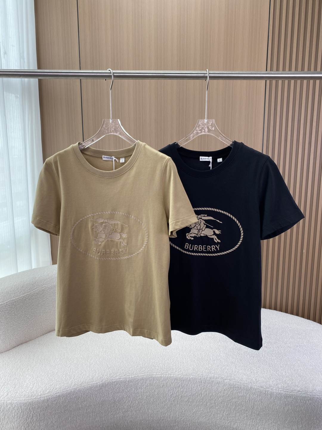 NO:873314,Burberry Equestrian Knight Embroidered Round Neck T-shirt Burberry's classic basic T-shirt, with the brand's iconic Equestrian Knight as the core design element, is both recognizable and practical. Core design features The iconic embroidery is an equestrian knight embroidery wrapped in a rope oval frame on the front, and the brand name 'BURBERRY' is embroidered below. It is the classic logo of the brand born in 1901, symbolizing courage and British elegance.  The basic version and color matching are round-neck short-sleeved tailoring, with a neat fit; available in khaki (same color embroidery) and black (light gold embroidery), low-key and refined, suitable for a variety of styles. Detailed craftsmanship The neckline is ribbed with neat stitching to ensure a stiff silhouette and comfortable wearing. Materials and origin Main fabric Pure cotton, breathable, skin-friendly, good sweat absorption, suitable for daily wear in spring and summer. Neck material 97 cotton + 3  Spandex (elastic fiber) increases the elasticity and deformation resistance of the collar, making it more comfortable to fit the neck. Brand background Burberry is a British luxury brand founded in 1856, with windbreakers, plaid and the equestrian knight logo as its core symbols. The equestrian knight pattern is one of the brand's earliest visual symbols, originating from the founder's tribute to the traditional British equestrian culture, and has now become one of the most recognizable elements of the brand. Outfit scene  Pair it with jeans/casual pants for daily casual use to create a relaxed American/British style; layer it with a denim jacket or knitted cardigan, suitable for the transitional season from spring to autumn; wear it under a suit for light business occasions, showing a low-key luxury taste.,,burberry,jeans,jackets & coats,T-shirt,tees,t-shirt,business suit,19860909Burberry 马术骑士刺绣圆领T恤 博柏利（Burberry）的经典基础款T恤,以品牌标志性的马术骑士（Equestrian Knight） 为核心设计元素,兼具辨识度与实穿性. 核心设计特征 标志性刺绣正面采用绳圈椭圆框包裹的马术骑士刺绣,下方绣有品牌名「BURBERRY」,是品牌1901年诞生的经典标识,象征勇气与英伦优雅. 版型与配色基础圆领短袖剪裁,版型合身利落；卡其色（同色系刺绣）与黑色（浅金色刺绣）两款,低调精致,适配多种风格. 细节工艺领口采用罗纹设计,缝线工整,保证版型挺括与穿着舒适度. 材质与产地 主体面料 纯棉,透气亲肤、吸汗性佳,适合春夏日常穿着. 领口材质97 棉 + 3 氨纶（弹性纤维）,增加领口弹性与抗变形能力,贴合颈部更舒适. 品牌背景 Burberry（博柏利）是创立于1856年的英国奢侈品牌,以风衣、格纹和马术骑士标识为核心符号. 马术骑士图案是品牌最早的视觉符号之一,源于创始人对英国传统马术文化的致敬,如今已成为品牌辨识度最高的元素之一. 穿搭场景 日常休闲搭配牛仔裤/休闲裤,打造轻松美式/英伦风； 叠穿搭配外搭牛仔外套、针织开衫,适配春秋过渡季； 轻商务场合作为西装内搭,低调彰显轻奢品味.,,burberry,jeans,jackets & coats,T-shirt,tees，t-shirt,business suit,,Women's clothing