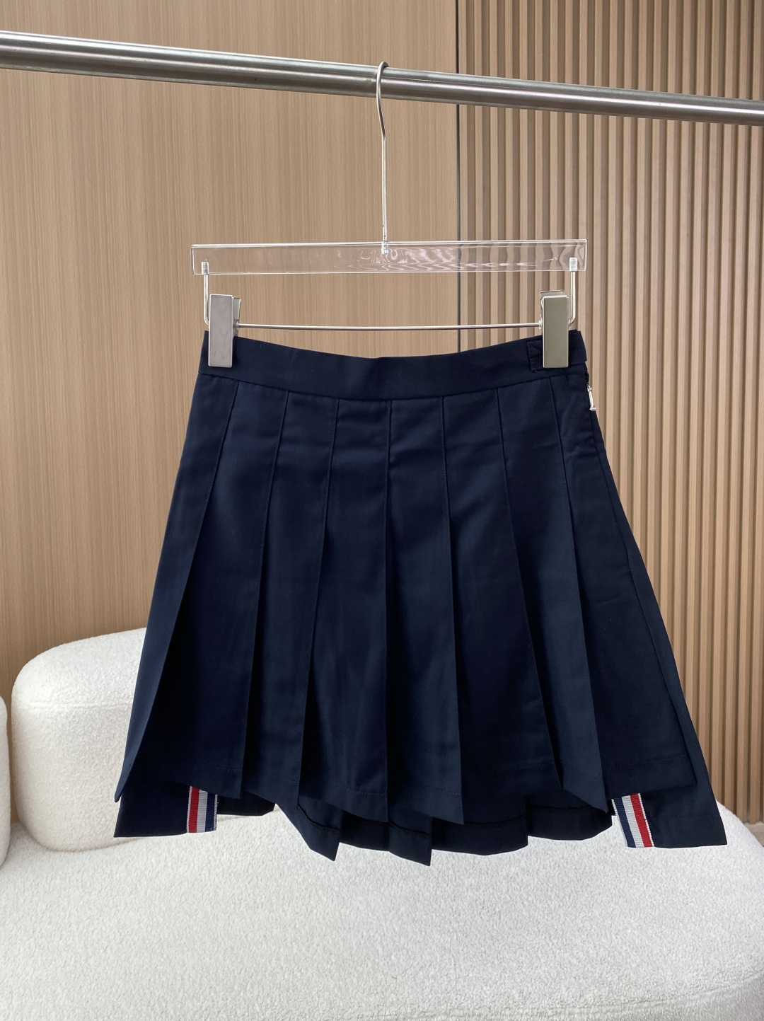 NO:840936,Thom Browne's classic preppy pleated skirt, with navy blue as the main color and the brand's iconic red, white and blue (RWB) three-color webbing elements, focuses on the American preppy (college elite) style. Design and appearance features The core version is high-waisted, A-line pleated cut, the skirt length is short, and the leg line is visually lengthened. It is the most recognizable bottoms version of Thom Browne. Iconic element  The waistband/skirt is embellished with red, white and blue webbing, which is the brand's classic identification symbol and echoes the American preppy style genes. The waistband is closed with two metal buttons + side zippers, one of the buttons has the brand's embossed logo, and the zipper pull is also decorated with red, white and blue details. Part of the irregular pleated skirt is longer, forming staggered layers. It is TB's signature 'high-low' design, which is more flexible.  Detailed texture: the fabric is crisp, the pleats are clearly defined, not easily deformed, the overall shape is neat and clean, and it is in line with the positioning of light luxury college style. Material: Wool (hair), crisp and drapey texture, good warmth retention, high-end matte texture, and is a commonly used fabric for high-end skirts.  The テープ part (webbing) polyester fiber (ポリエステル) enhances the wear resistance and styling effect of the webbing. The lining (lining) cupro fiber (キニプラ) is skin-friendly, breathable, anti-static, and improves wearing comfort. Made in MADE IN ITALY (Made in Italy), in line with high-end line production standards. Washing requirements  Do not wash, bleach, or tumble dry at high temperatures. It is recommended to iron with a low-temperature cloth (or professional dry cleaning). Do not expose to the sun to avoid shrinkage and deformation of the wool. Wearing scenarios and matching suggestions. Classic college style white shirt + navy knitted cardigan + loafers + mid-calf socks, restoring the American campus preppy style, suitable for daily travel and campus scenes. Light and sophisticated commuter style short blazer + pointed high heels + mini armpit bag, smart and elegant, suitable for light business and dating occasions in the workplace.  To keep warm, wear safety pants inside to prevent exposure, and wear a long windbreaker/coat outside, which is suitable for the cooler weather in spring and autumn and adds layering to the look. Match the color matching with white and gray items, or use small red accessories (such as hairbands, earrings) to echo the red, white and blue webbing to enhance style recognition. Washing and care instructions 1. Core recommendations: Professional dry cleaning is recommended for wool materials to avoid shrinkage and wrinkle deformation caused by washing. 2.  For daily cleaning, only local stains can be patted lightly with a wet towel, and avoid vigorous rubbing. 3. Ironing requires a cloth and low temperature ironing (≤110℃). Do not iron the wool surface directly to prevent aurora. 4. For hanging storage, use panniers to keep pleats in shape and avoid extrusion.,,thom browne,loafers,high heels,skirts,jackets & coats,shirts,business suit,earrings,19860909Thom Browne（汤姆·布朗）经典学院风百褶短裙,以藏青色为主色调,以及品牌标志性的红白蓝（RWB）三色织带元素,主打美式Preppy（学院精英）风格. 设计与外观特征 核心版型高腰A字百褶剪裁,裙长偏短,视觉上拉长腿部线条,是Thom Browne最具辨识度的下装版型. 标志性元素 腰头/裙摆处点缀红白蓝三色织带,是品牌的经典识别符号,呼应美式学院风基因. 腰头采用两枚金属纽扣+侧拉链闭合,其中一枚纽扣带有品牌浮雕标识,拉链头也装饰有红白蓝细节. 不规则百褶裙摆部分裙摆更长,形成错落层次,是TB标志性的“高低摆”设计,更显灵动. 细节质感面料挺括,百褶定型清晰,不易变形,整体利落干净,符合轻奢学院风定位. 材质 表地（面料）羊毛（毛）,质感挺括垂坠,保暖性佳,自带高级哑光质感,是高端裙装常用面料. テープ部分（织带）聚酯纤维（ポリエステル）,增强织带耐磨度与定型效果. 裏地（里料）铜氨纤维（キニプラ）,亲肤透气、防静电,提升穿着舒适度. 产地MADE IN ITALY（意大利制造）,符合高端线生产标准. 洗涤要求 不可水洗、不可漂白、不可高温烘干 建议低温垫布熨烫（或专业干洗） 不可暴晒,避免羊毛缩水、变形 穿着场景与搭配建议 学院风经典搭白衬衫+藏青针织开衫+乐福鞋+中筒袜,还原美式校园Preppy风格,适合日常出行、校园场景. 轻熟通勤风短款西装外套+尖头高跟鞋+迷你腋下包,干练优雅,适配职场轻商务、约会场合. 叠穿保暖法内搭安全裤防走光,外搭长款风衣/大衣,适配春秋微凉天气,增加造型层次感. 配色呼应可搭配白色、灰色单品,或用红色小配饰（如发带、耳环）呼应红白蓝织带,强化风格辨识度. 洗涤与保养说明 1. 核心建议羊毛材质建议专业干洗,避免水洗导致缩水、褶皱变形. 2. 日常清洁仅局部污渍可用湿毛巾轻拍,避免大力揉搓. 3. 熨烫要求需垫布低温熨烫（≤110℃）,不可直接熨烫羊毛表面,防止产生极光. 4. 存放悬挂存放,使用裙撑保持百褶定型,避免挤压.,,thom browne,loafers,high heels,skirts,jackets & coats,shirts,business suit,earrings,,Women's clothing