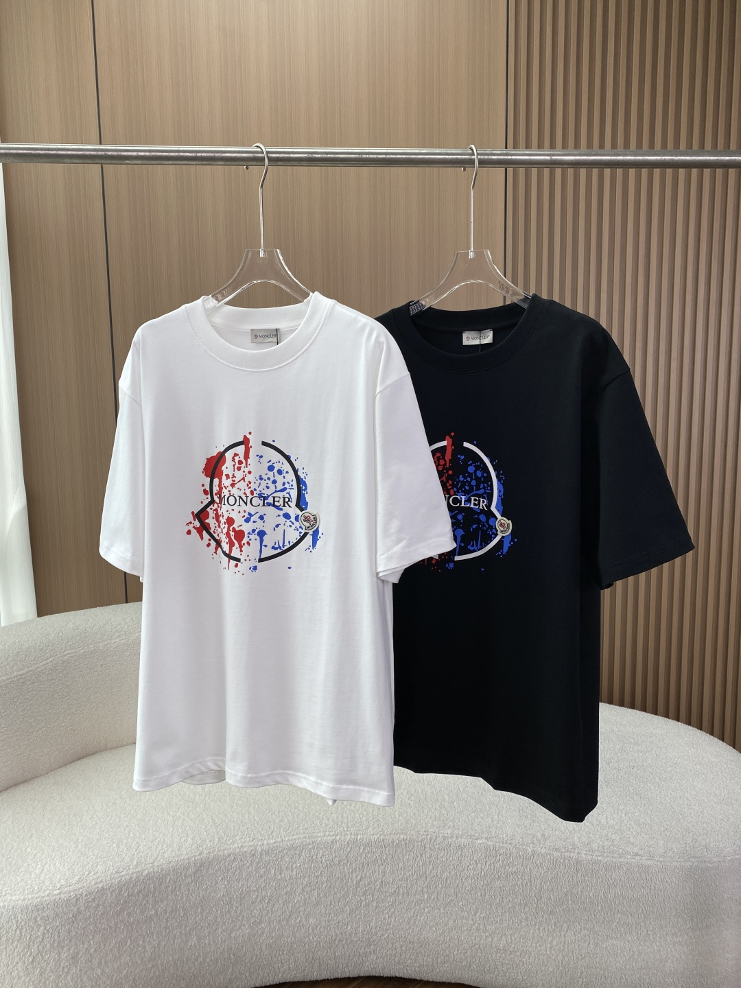 NO:827800,The core element of the Moncler short-sleeved T-shirt with contrasting ink splash printing is a large red and blue splash ink logo, with 'MONCLER' letters printed in the middle, and a Moncler mini badge sewn on the right side. The overall style is biased toward street fashion and light luxury. The colors are black and white. The black version has a white frame + red and blue splash ink logo, and the white version has a black frame + red and blue splash ink, suitable for different wear scenarios.  Details: The neckline is a ribbed round neck, the cuffs are flat design, and the hem is cut with a straight edge. The oversize version has a lower shoulder line and a longer length, which is suitable for creating a casual and lazy street style and is more tolerant to the figure. Fabric composition: 95 cotton + 5 spandex Performance features: High cotton content, ensuring breathability and sweat absorption, suitable for spring and summer wear;  5. The addition of spandex improves the elasticity of the fabric and reduces the probability of deformation and wrinkles after washing. The medium-thick T-shirt fabric will not be too thin and leaky. Wearing scenarios: Daily casual wear alone with denim shorts, overalls, sports pants, suitable for street, campus, commuting and other scenes; layered in spring and autumn, worn under denim jackets, baseball uniforms, work jackets, to increase the sense of layering;  Shoes and bags are suitable for dad shoes, sneakers, sports shoes, and baseball caps and cross-body bags can enhance the sense of fashion. Washing and maintenance It is recommended to hand wash or gentle machine wash with cold water temperature below 30℃ to avoid high temperature causing the print to fall off and the fabric to shrink; drying method is reversed to avoid direct sunlight, which may cause the fabric to turn yellow and the print to fade;  Ironing Note: If you need to iron, you need to iron it at low temperature with a cloth. It is forbidden to iron the printed area directly.19860909蒙口Moncler撞色泼墨印花短袖T恤 核心元素采用红蓝泼墨撞色大logo,中间叠加「MONCLER」字母印花,右侧缝制Moncler迷你徽章标,整体风格偏向街头潮流与轻奢感. 色彩选择黑色、白色两款基础色,黑色款logo为白框+红蓝泼墨,白色款为黑框+红蓝泼墨,适配不同穿搭场景. 细节处理领口为罗纹圆领,袖口为平口设计,下摆为直边剪裁 版型宽松落肩（Oversize）版型,肩线偏下、衣长偏长,适合打造休闲慵懒的街头风格,对身材包容性较强. 面料成分 面料95棉+ 5氨纶 性能特点 棉含量高,保证了透气吸汗性,适合春夏季节穿着； 5氨纶添加,提升了面料弹性,减少洗后变形、起皱的概率,中等偏厚的T恤面料,不会过于轻薄漏肤. 穿搭场景 日常休闲单穿搭配牛仔短裤、工装裤、运动束脚裤,适配街头、校园、通勤等场景； 叠穿搭配春秋季内搭于牛仔外套、棒球服、工装夹克下,增加层次感； 鞋包适配搭配老爹鞋、板鞋、运动鞋,搭配棒球帽、斜挎包可强化潮流感. 洗涤保养 水温控制建议30℃以下冷水手洗或轻柔机洗,避免高温导致印花脱落、面料缩水； 晾晒方式反面晾晒,避免阳光直射导致面料发黄、印花褪色； 熨烫注意如需熨烫,需垫布低温熨烫,禁止直接熨烫印花区域.,,versace,Moncler,sneakers,satchels,crossbody bags,shorts,jackets & coats,jackets & coats,T-shirt,tees，t-shirt,hats,,Women's clothing