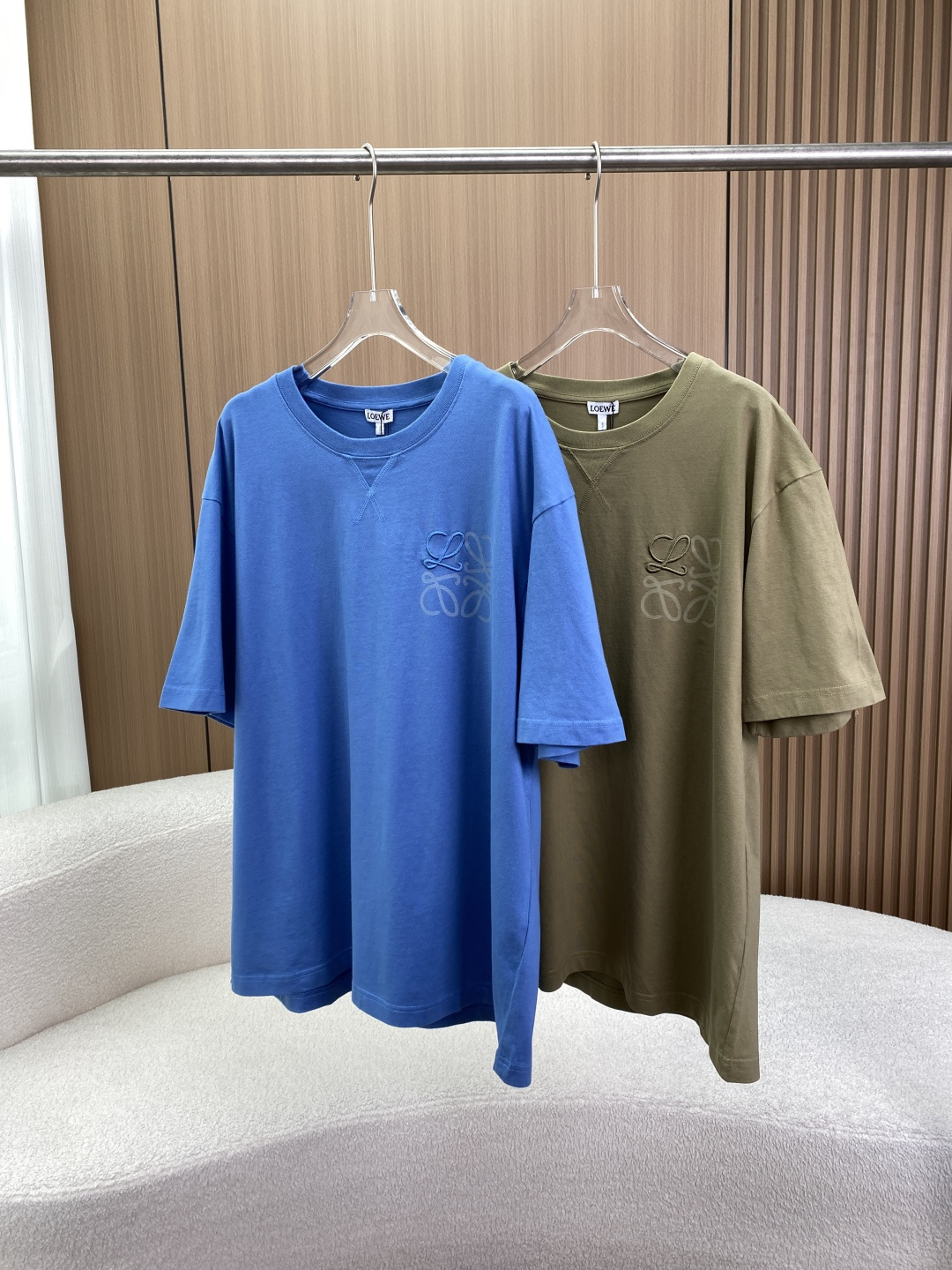 NO:827820,(Original customization) LOEWE classic logo embroidered T-shirt 1. Core identity and brand heritage 1. Centennial luxury gene Founded in 1846, the Spanish century-old luxury brand originally started with top-notch leather craftsmanship and was once a royal supplier to the Spanish royal family. Although it has now turned to ready-made clothing, each item still retains the aristocratic pedigree with extreme control over details. 2. Iconic logo  The Anagram logo on the chest is the soul symbol of LOEWE. It was designed by Spanish artist Vicente Vela. It was originally an intertwining of four letters 'L' and evolved into today's highly artistic spiral pattern. Different from the large logo that fills the screen, this low-key embroidery is the best way to show your taste. 2. Physical details 1. Material  The main fabric of high-quality cotton is 100% cotton. This fabric is not only skin-friendly and breathable, but also has been precision woven, has sufficient weight, feels soft and waxy but is wide but not soft, and will not deform after long-term wear. 2. Process highlights: 'X'-shaped triangle needle process on the neckline. Looking at the inside of the collar, the classic V-neck/triangle needle reinforcement process is used. This is the standard feature of high-end T-shirts. It is not only beautiful, but also effectively prevents the collar from becoming larger and looser after washing, which greatly extends the service life of the clothing.  Two-color/three-dimensional embroidery The Anagram Logo on the chest adopts three-dimensional embroidery technology. The green model in the picture is a contrasting design (dark solid embroidery + light color virtual printing/transparent color), and the blue model is embroidery of the same color and depth. This technology is more three-dimensional than ordinary flat embroidery, with a delicate touch and strong gloss. 3. Color matching 1. Color scheme Serenity blue is a low-saturation haze blue/grey blue, which is very white, suitable for spring and summer, and has a refreshing and high-end feel.  Army green/khaki is an earth color, very textured, mature and stable. Men can wear it to show their aura, while women can wear it to show their casualness. 2. The version is a loose shoulder version (Oversize/Relaxed Fit). It is not picky about the figure, it can not only modify the shoulders, but also hide the fat. It is the same style for men and women, and it is very popular for couples. 4. Wearing scenarios 1. Versatile scenarios: Pair with original color jeans and white shoes every day, refreshing and not artificial.  Wear it with casual suits, leather jackets or knitted cardigans for light business, which instantly enhances the layering of your outfit, upgrading it from a 'T-shirt' to a 'texture outfit'. Wear it trendy with cycling pants or bare legs to create a Cityboy/Sweet and Cool Girl style.,,loewe,loewe,versace,jeans,tees,t-shirt,leather jacket,business suit,19860909（原版定制） LOEWE（罗意威） 经典Logo刺绣T恤 一、 核心身份与品牌底蕴 1. 百年奢侈基因 创立于1846年的西班牙百年奢牌,最初以顶级皮革工艺起家,曾是西班牙王室御用供应商.如今虽转向成衣,但每件单品仍保留着对细节极致把控的贵族血统. 2. 标志性Logo 胸前的Anagram标识是LOEWE的灵魂符号.它由西班牙艺术家Vicente Vela设计,最初是四个字母“L”的交织,演变成今天极具艺术感的螺旋花纹.区别于满屏大Logo,这种低调刺绣是彰显品位的最佳方式. 二、 实物细节 1. 材质 高品质棉主面料为全棉.这种面料不仅亲肤透气,且经过精密纺织,克重足,手感软糯但挺阔不软塌,久穿不变形. 2. 工艺亮点 领口“X”型三角针工艺 观察领口内侧,采用了经典的V领/三角针加固工艺.这是高端T恤的标配,不仅美观,更能有效防止领口洗涤后变大、松垮,极大延长了衣物的使用寿命. 双色/立体刺绣 胸前的AnagramLogo采用了立体刺绣工艺.图中绿色款为撞色设计（深色实绣+浅色虚印/透色）,蓝色款为同色系深浅刺绣.这种工艺比普通平绣更具立体感,触感细腻且光泽感强. 三、 配色 1. 配色方案 静谧蓝低饱和度的雾霾蓝/灰蓝,非常显白,适合春夏,自带清爽高级感. 军绿/卡其色属于大地色系,非常有质感,成熟稳重,男士穿着显气场,女士穿着显随性. 2. 版型 属于宽松落肩版型（Oversize/Relaxed Fit）.不挑身材,既能修饰溜肩,又能隐藏赘肉,男女同款,情侣穿搭非常出片. 四、 穿搭场景 1. 全能场景 日常搭配原色牛仔裤、小白鞋,清爽不刻意. 轻商务外搭休闲西装、皮衣或针织开衫,瞬间提升穿搭层次感,从“T恤”升级为“质感穿搭”. 潮流搭配骑行裤或光腿穿,打造Cityboy/甜酷Girl风格.,,loewe,loewe,versace,jeans,tees，t-shirt,leather jacket,business suit,,Women's clothing