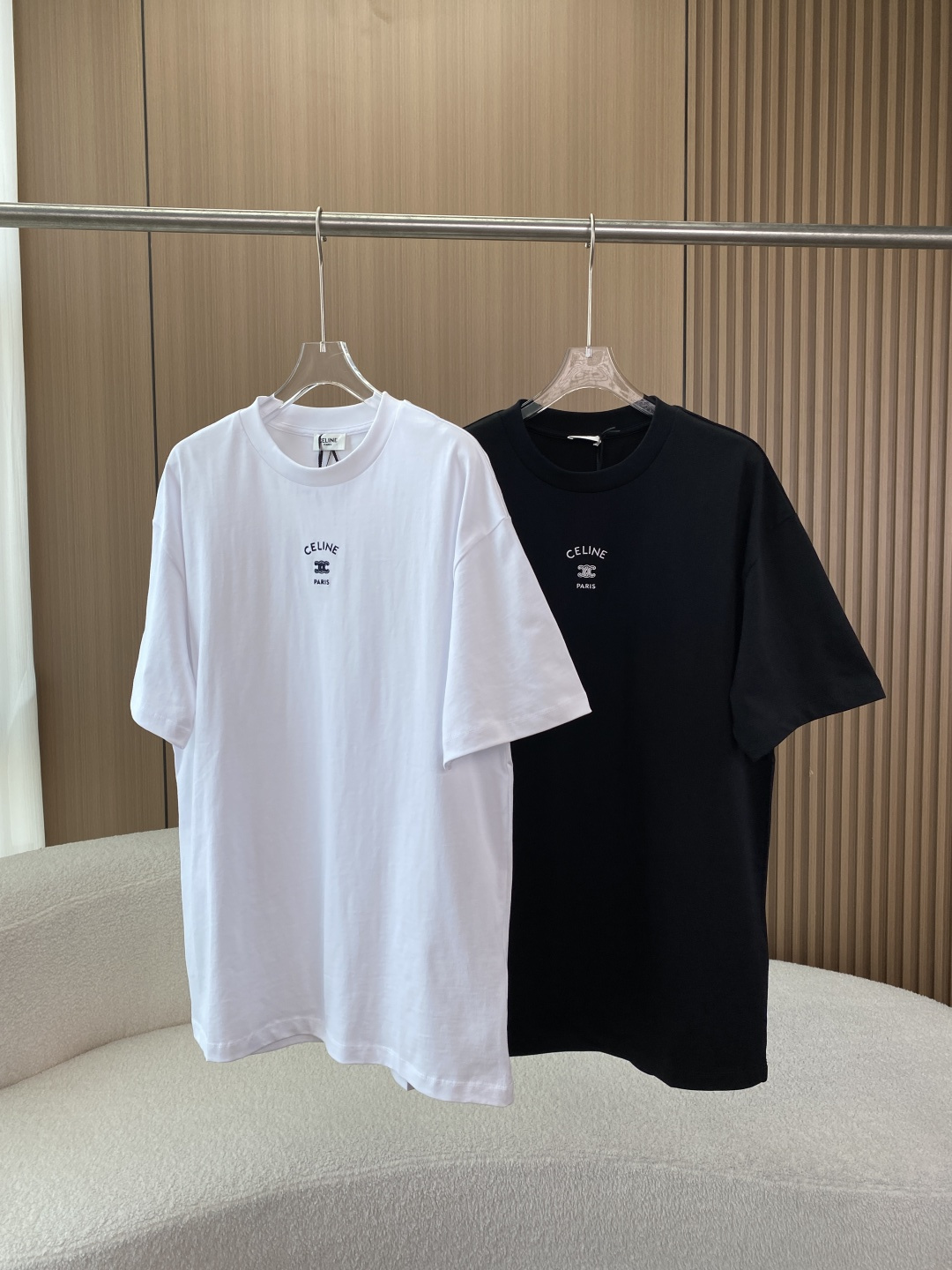 NO:808326,(Men’s version) Really awesome CELINE Arc de Triomphe embroidered round neck short-sleeved T-shirt. The classic Arc de Triomphe embroidered round neck short-sleeved T-shirt launched by the French luxury brand CELINE is an iconic entry-level item in the French minimalist style under the leadership of the brand’s current creative director Hedi Slimane. It is also a popular style in global luxury casual wear in recent years. 1. Brand background and design concept CELINE is developed by Céline  Vipiana was founded in Paris in 1945. It initially started with high-end custom shoes, and then gradually developed into a full-category luxury brand. After Hedi Slimane took over as the creative director in 2018, the brand style returned to pure French minimalism, retro high-end, and this T-shirt is the core classic design of that period.  In terms of design, the single product uses the brand's iconic Triomphe symbol as the core element - this symbol is derived from the chain pattern of the Arc de Triomphe in Paris and is a brand totem inherited by CELINE for decades. The T-shirt adopts an arc-shaped arrangement of 'CELINE' centered on the chest.  PARIS' letter embroidery, with three-dimensional Arc de Triomphe double C lock embroidery in the middle. There is no unnecessary decoration on the whole. The extremely simple design highlights the brand recognition. It not only conforms to CELINE's 'unobtrusive high-end sense' brand tone, but also takes into account the practicality of casual clothing. At the same time, it adopts the same loose version for men and women, covering the dressing needs of all genders. 2. Version and tailoring details  This T-shirt adopts a loose, straight-leg style with dropped shoulders. It is a more conventional oversize cut rather than an extremely loose style. It is very tolerant to the body shape and can be worn by normal figures to make them feel loose. It can be worn by slightly chubby figures to modify the figure. It can be adapted to both men and women.  The neckline adopts a high-weight rib round neck design with a moderate width, which is neither too tight nor too loose. The elasticity and resilience of the ribs are excellent, and with the brand's exclusive reinforcement strips on the inside of the neckline, it can still remain stiff after multiple washes, completely avoiding the problem of collapsed collars.  The straight cut of the body and the dropped shoulder design weaken the sense of restraint of the shoulder line and create a lazy and relaxed wearing atmosphere; the length of the garment is moderate, and it can cover the upper edge of the buttocks when worn normally. It can be worn alone or tucked into the corners according to needs, adapting to a variety of dressing styles. The sleeves are of regular short sleeve length, and the cuffs are made of double-strand seaming technology, which is neatly routed and has no problems with threading or curling; the sleeves are loose, not tight on the arms, and suitable for various arm circumferences. 3. Fabric and process details  1. The fabric material is made of high-count combed heavyweight pure cotton, with a gram weight of about 250g. The fabric is customized from the Portuguese factory. The fabric is thick and crisp, not thin and soft. It also has the skin-friendly and breathable characteristics of pure cotton. It will not be stuffy or sweaty when worn in summer. The fabric has been pre-shrunk. After multiple washings, there is no obvious shrinkage or deformation, and the durability is maximized. 2. Embroidery process  The chest LOGO adopts high-density three-dimensional embroidery technology, and the stitches are extremely tight and full. Each stitch is evenly and neatly routed, with no jumps, missing stitches, or burrs. The letters are CELINE's exclusive brand fonts, and the arc and spacing strictly follow the brand standards. The Arc de Triomphe is double in the middle.  The C-lock pattern has sharp and clear lines; the embroidery edges are flat, and it fits the fabric very well without the risk of bulging or falling off. The white model uses black embroidery, and the black model uses white embroidery. The contrasting design makes the LOGO eye-catching but not ostentatious, which perfectly fits the minimalist tone of the brand.  Wear style and scene adaptation: The most classic way to wear casual style in daily life, wear it alone, with straight jeans, wide-leg jeans or casual shorts, white shoes, sneakers, moral training shoes, to create a French relaxed daily wear, suitable for shopping, dating, and daily travel; girls can pair with cycling pants and shark pants to create a hot girl style, and boys can pair with cargo shorts to create a casual street style.  The commuting workplace style is used as an inner wear. Pair it with a suit jacket, windbreaker, leather jacket, trousers, cigarette pants, and a straight skirt to create a simple and advanced commuting look that is both formal and fashionable in the workplace. It is suitable for offices, business meetings and other scenes.  For street fashion, choose one size larger to create an oversize look. Pair with overalls, leggings, wide-leg jeans, dad shoes, sneakers, and accessories such as necklaces and bracelets to enhance the sense of hierarchy. It is suitable for fashionable people to go out and music festivals. For French retro style, pair it with high-waisted straight jeans, Mary Jane shoes, loafers, berets, silk scarves and other accessories to restore the pure French retro style. It perfectly fits the CELINE brand tone and is suitable for travel, photography and other scenes.  6. Care and Maintenance Guide In order to keep the shape, embroidery and fabric of the T-shirt intact, correct care methods must be followed. It is recommended to wash the T-shirt gently by hand with warm water below 30℃, or wash it in the gentle mode of the washing machine. When washing, be sure to turn the T-shirt inside out to avoid direct friction on the embroidery, which may cause deformation and fall off. Wash it with clothes of the same color to avoid staining. It is prohibited to use bleach and strong alkaline detergents, and the soaking time should not exceed 15 minutes.  After drying and washing, gently squeeze out the water and do not wring it out hard; turn the T-shirt inside out and dry it in a cool and ventilated place away from direct sunlight to prevent the fabric from yellowing and the embroidery from fading; avoid using thin hangers to hang the neckline to dry. It is recommended to lay it flat to dry or hang it on a wide-shoulder hanger to prevent the neckline from deforming.  When ironing, turn the T-shirt over and iron it with low-temperature steam. It is forbidden to iron the embroidery part directly to avoid high temperature damage to the embroidery. When ironing, operate it gently and do not press hard to prevent the fabric from deforming. Store it on a wide-shoulder hanger for daily storage, avoid folding and squeezing, and keep the pattern crisp; store it in a dry and ventilated wardrobe to avoid moisture and mold. Do not place it with sharp objects to prevent snagging.,,celine,celine,versace,loafers,mary  jane,sneakers,skirts,shorts,jeans,jackets & coats,T-shirt,tees,t-shirt,leather jacket,business suit,necklace,bracelet,hats,19860909（男款）实物超赞 赛琳CELINE凯旋门刺绣圆领短袖T恤 法国奢侈品牌CELINE（思琳）推出的经典凯旋门刺绣圆领短袖T恤,是品牌现任创意总监Hedi Slimane主导后,法式极简风格的标志性入门单品,也是近年全球奢侈品休闲服饰中的热门款. 一、品牌背景与设计理念 CELINE由Céline Vipiana于1945年在巴黎创立,最初以高级定制鞋履起家,后逐步发展为全品类奢侈品牌.2018年Hedi Slimane接任创意总监后,品牌风格回归纯粹的法式极简、复古高级,这款T恤正是该时期的核心经典设计. 设计上,单品以品牌标志性的凯旋门（TRIOMPHE）符号为核心元素——该符号源自巴黎凯旋门的锁链纹样,是CELINE传承数十年的品牌图腾.T恤采用胸前居中的弧形排列“CELINE PARIS”字母刺绣,中间搭配立体凯旋门双C锁扣刺绣,整体无多余装饰,用极致简约的设计凸显品牌辨识度,既符合CELINE“不张扬的高级感”品牌调性,又兼顾了休闲服饰的实用性,同时采用男女同款的宽松版型,覆盖全性别穿搭需求. 二、版型与剪裁细节 这款T恤采用宽松落肩直筒版型,属于偏常规的oversize剪裁,而非极端宽松的款式,对身材包容度极高正常身材可穿出松弛感,微胖身材可修饰身形,男女均可适配. 领口采用高克重罗纹圆领设计,领口宽度适中,既不会过紧勒颈,也不会过松垮塌；罗纹的弹性与回弹性极佳,搭配领口内侧的品牌专属加固包条,多次洗涤后仍能保持挺括,完全避免塌领问题. 衣身直筒剪裁搭配落肩设计,弱化肩线束缚感,打造慵懒松弛的穿搭氛围；衣长适中,正常穿着可盖住臀部上缘,可直接单穿,也可根据需求塞衣角,适配多种穿搭风格. 袖部常规短袖长度,袖口采用双股线锁边工艺,走线工整,无脱线、卷边问题；袖型宽松,不紧绷手臂,适配各类臂围. 三、面料与工艺细节 1. 面料材质 采用高支精梳重磅纯棉,克重约250g,为葡萄牙原厂定制面料面料厚实挺括,无单薄软塌感,同时兼具纯棉的亲肤、透气特性,夏季穿着不闷热、出汗不贴身；面料经过预缩水处理,多次洗涤后无明显缩水、变形,耐用性拉满. 2. 刺绣工艺 胸前LOGO采用高密度立体刺绣工艺针脚极其紧密饱满,每一针走线均匀工整,无跳线、漏针、毛边问题；字母为CELINE专属品牌字体,弧度、间距严格遵循品牌标准,中间凯旋门双C锁扣图案,线条锐利清晰；刺绣边缘平整,与面料贴合度极高,无凸起、脱落风险.白色款采用黑色刺绣,黑色款采用白色刺绣,撞色设计让LOGO醒目却不张扬,完美契合品牌极简调性. 穿搭风格与场景适配 日常休闲风最经典的穿法,直接单穿,搭配直筒牛仔裤、阔腿牛仔裤或休闲短裤,脚踩小白鞋、板鞋、德训鞋,打造法式松弛感日常穿搭,适合逛街、约会、日常出行；女生可搭配骑行裤、鲨鱼裤打造辣妹风,男生可搭配工装短裤打造街头休闲风. 通勤职场风作为内搭,搭配西装外套、风衣、皮衣,下搭西裤、烟管裤、直筒半裙,打造简约高级的通勤造型,既符合职场正式感,又不失时尚感,适合办公室、商务会面等场景. 街头潮流风选择大一号尺码打造oversize造型,搭配工装裤、束脚裤、阔腿牛仔裤,脚踩老爹鞋、运动鞋,搭配项链、手链等配饰,提升层次感,适合潮人出街、音乐节等场景. 法式复古风搭配高腰直筒牛仔裤、玛丽珍鞋、乐福鞋,搭配贝雷帽、丝巾等配饰,还原纯正法式复古穿搭,完美契合CELINE品牌调性,适合出游、拍照等场景. 六、护理与保养指南 为保持T恤版型、刺绣与面料的完好,需遵循正确护理方法 洗涤建议30℃以下温水轻柔手洗,或洗衣机轻柔模式洗涤；洗涤时务必将T恤反面翻过来,避免刺绣直接摩擦导致变形脱落,与同色衣物同洗,避免染色；禁止使用漂白剂、强碱性洗涤剂,浸泡时间不超过15分钟. 晾晒洗涤后轻轻挤干水分,禁止用力拧干；将T恤反面翻过来,在阴凉通风处晾干,禁止阳光直射,防止面料发黄、刺绣掉色；避免用细衣架撑挂领口晾晒,建议平铺晾干或宽肩衣架悬挂,防止领口变形. 熨烫熨烫时将T恤反面翻过来,用低温蒸汽熨烫,禁止直接熨烫刺绣部分,避免高温损伤刺绣；熨烫时轻柔操作,禁止用力按压,防止面料变形. 存放日常用宽肩衣架悬挂存放,避免折叠挤压,保持版型挺括；存放于干燥通风衣柜,避免潮湿发霉,禁止与尖锐物品同放,防止勾丝.,,celine,celine,versace,loafers,mary jane,sneakers,skirts,shorts,jeans,jackets & coats,T-shirt,tees，t-shirt,leather jacket,business suit,necklace,bracelet,hats,,Women's clothing