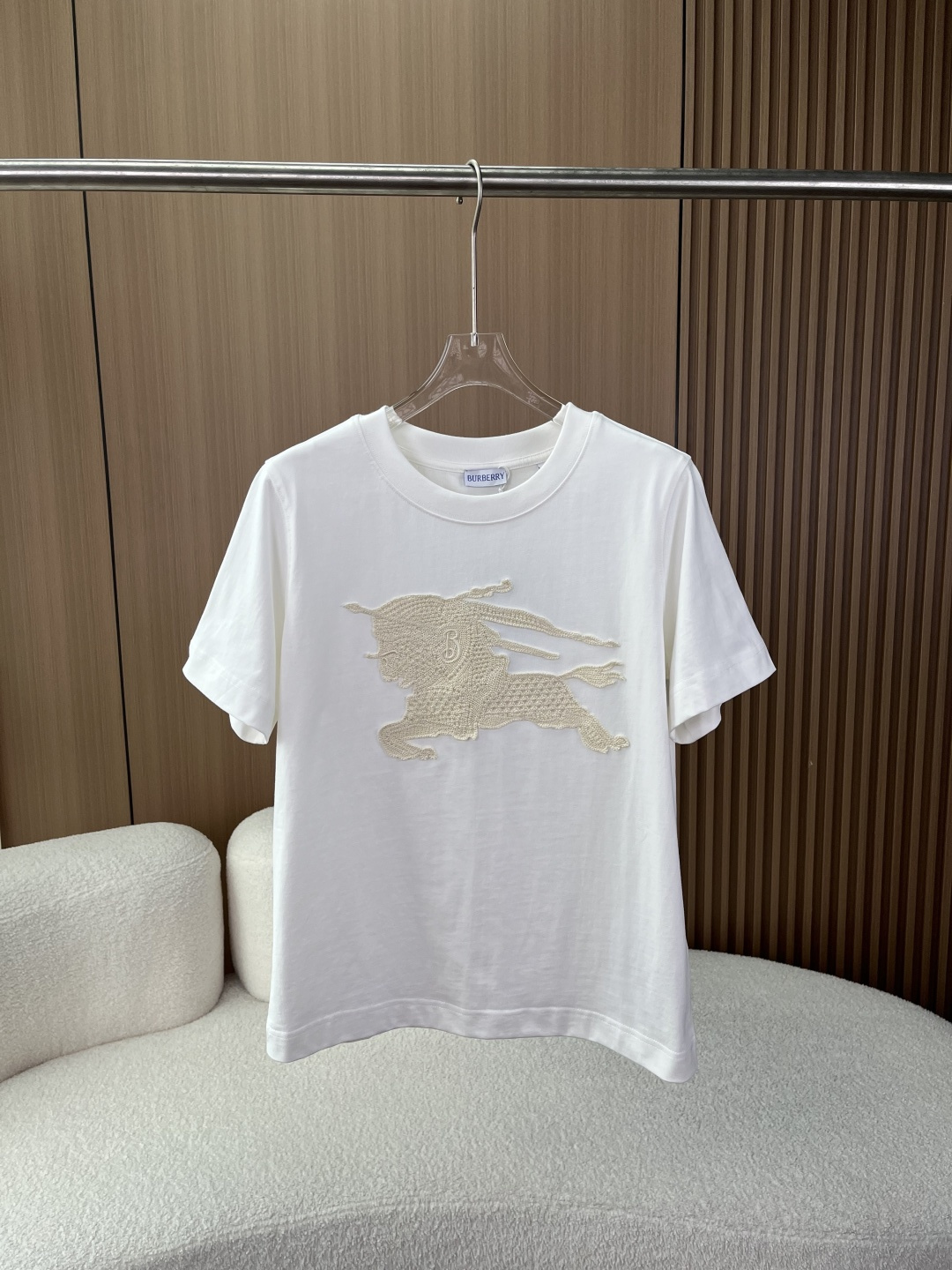 NO:835077,(Original customization) Burberry Women's Crochet Knight Logo T-shirt!  The core craftsmanship uses hand-made crochet/hollow embroidery technology on the chest to present the brand's iconic Equestrian Knight logo (EKD). The off-white crochet pattern and off-white background form a high-end texture of the same color. The letter 'B' on the knight's shield has clear details and exquisite three-dimensional craftsmanship. The version fits the right shoulder, is not picky, and is suitable for daily leisure, light business and other scenarios. The color is off-white, clean and versatile, weakening the publicity of the logo, and making it more low-key, light and luxurious. 2.  Fabrics and Ingredients The main fabric is pure cotton, which is skin-friendly and breathable. The high-gram weight material ensures a crisp feel and is not easy to deform. The collar fabric is 97 cotton + 3 spandex, which improves the elasticity of the collar and prevents the collar from collapsing after long-term wear. The decorative polyester fiber ensures the stiffness and shape of the crochet and is not easy to deform. Washing instructions: Gentle machine wash at 30°C. Bleaching, tumble drying, and high-temperature ironing are prohibited. It is recommended to wash the reverse side to avoid damage to the crochet. Design background and process 1.  Traceability of brand elements The Equestrian Knight logo (EKD) is the core symbol of the brand used by Burberry since 1901, representing the brand's British equestrian culture and craftsmanship. This model reinterprets the traditional logo with hand-crocheted technology, blending retro craftsmanship and modern casual style, and is a representative design of the brand's classic elements that are younger. 2. Craftsmanship highlights The crochet pattern adopts a hollow weaving structure, which has both three-dimensionality and breathability. It is visually more layered and textured, different from ordinary printed models.  The same color design weakens the presence of the logo and is suitable for consumers who pursue low-key luxury and do not like exaggerated logos. Outfit and care suggestions 1. Suitable outfits The style is suitable for casual, commuting, and light business. It can be worn alone or layered with denim jackets, suits, and windbreakers. It can be paired with jeans, casual trousers, and shorts to easily create a relaxed and high-end look.,,burberry,burberry,shorts,jeans,jackets &  coats,tees,t-shirt,business suit,19860909（原版定制） Burberry 巴宝莉女款钩花骑士徽标T恤 ！ 核心工艺胸前采用手工钩编/镂空刺绣工艺,呈现品牌标志性马术骑士徽标（EKD）,米白色钩花与米白底色形成同色系高级质感,骑士盾牌处的字母'B'细节清晰,工艺精致立体. 版型合身正肩版型,不挑身材,适配日常休闲、轻商务等多场景. 配色米白色,干净百搭,弱化logo的张扬感,更显低调轻奢. 2. 面料与成分 主体面料纯棉,亲肤透气,高克重材质保证挺括感,不易变形. 衣领面料97棉+3氨纶,提升领口弹性,久穿不易塌领. 装饰部分聚酯纤维,保证钩花的挺括度与造型感,不易变形. 洗涤说明30℃水温轻柔机洗,禁止漂白、滚筒烘干、高温熨烫,建议反面洗涤,避免钩花勾丝损坏. 设计背景与工艺 1. 品牌元素溯源 马术骑士徽标（EKD）是Burberry自1901年起使用的品牌核心符号,代表品牌的英伦马术文化与匠心工艺.该款将传统徽标以手工钩编工艺重新演绎,融合了复古手工艺与现代休闲风格,是品牌经典元素年轻化的代表设计. 2. 工艺亮点 钩花采用镂空编织结构,兼具立体感与透气性,视觉上更具层次与质感,区别于普通印花款. 同色系设计弱化了logo的存在感,适合追求低调轻奢、不喜欢夸张大标的消费者. 穿搭与护理建议 1. 穿搭适配 风格休闲、通勤、轻商务多场景适配,可单穿、叠穿牛仔外套、西装、风衣. 搭配搭配牛仔裤、休闲西裤、短裤均可,轻松打造松弛感、高级感穿搭.,,burberry,burberry,shorts,jeans,jackets & coats,tees，t-shirt,business suit,,Women's clothing