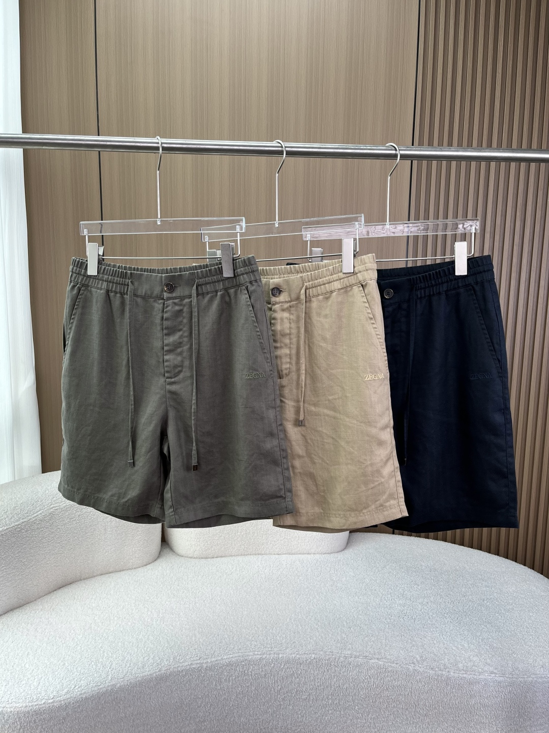 NO:826137,(Tencel linen shorts) ZEGNA (Zegna) linen and Tencel blended drawstring shorts 1. Brand and series positioning Brand ZEGNA (Zegna), the world's top luxury men's clothing brand founded in Italy in 1910, with high-end fabric research and development and Italian tailoring as its core competitiveness, is the benchmark brand of 'old money style' men's clothing. The series it belongs to Oasi  Lino (Emenia Zegna Oasis Linen) series is the brand's iconic high-end leisure line, focusing on sustainable and traceable European top linen fabrics, inheriting the brand founder's concept of vertically integrated textile production. 2. Detailed explanation of fabric ingredients and processes Ingredient ratio 70 Linen (LINEN) + 30 TENCEL (Tencel, Lyocell fiber) Fabric advantages 70 Linen natural plant fiber, breathable, moisture-absorbent, sweat-wicking, and UV-resistant  Wearing it in summer brings a cool feeling, it does not make you sweat for a long time, and it does not stick to your body after sweating. 30 Tencel is a regenerated cellulose fiber extracted from wood pulp. It has a strong drape, is soft and smooth, has excellent wrinkle resistance, is skin-friendly and breathable, and neutralizes the roughness of linen. The fabric feels silky and smooth, and the upper body hangs smoothly without collapsing, greatly reducing wrinkles.  The fabric technology adopts twill weave, the fabric has a delicate texture, and the luster is natural and soft, which is different from the cheap feeling of ordinary plain linen; after pre-shrinking treatment, the shrinkage rate is very low after wearing, and the shape is stable. 3. Version and design details Regular fit (regular straight version), five-quarter length (knee-length design), straight leg placket, not picky about the figure, good tolerance for the waist, abdomen and thighs, suitable for most Asian male figures. Waist design  The double-layered elastic waistband and built-in drawstring allow you to freely adjust the waistline, taking into account both comfort and fit, so you won’t feel restricted after sitting for long periods of time; the placket adopts a “button + invisible zipper” design, and the buttons are brand-customized natural horn buttons with clear texture and thick texture; the end of the drawstring is decorated with a metal square pendant, with a matte texture, which improves the sophistication of details and avoids burrs on the drawstring;  The inside of the waist is edged in contrasting colors (khaki models are edged in burgundy) and 360° edging strips improve wearing comfort and durability. Pocket design: Slanted pockets on both sides of the front, deep enough to hold mobile phones and wallets without slipping; single pocket on the back waist, with a flap design, and the brand's circular Z logo embossed on top of the flap, which is low-key and recognizable; double-line seams are made on the edges of the pockets, with neat craftsmanship, strong load-bearing capacity, and not easy to deform. Logo design  The ZEGNA brand logo is embroidered in the same color on the left trouser leg on the front, with fine stitching, neat routing, no overflow threads, and no jumpers. It is highly integrated with the fabric and is low-key and unobtrusive; the circular embroidered logo on the back waist is in line with the design concept of 'low-key luxury' in the old money style. Color selection: Navy blue has the strongest sense of business, suitable for commuting, light business, and formal leisure occasions; Army green has a full casual feel, suitable for daily travel, outdoor, and vacation;  Khaki is a versatile color, suitable for all casual and business scenes, regardless of skin color. 2. Guide to dressing in all scenes (different styles + different occasions) 1. Light business commuting style (suitable for offices and business meetings) Matching formula ZEGNA linen shorts + same brand linen shirt/POLO shirt + loafers/derby shoes + simple belt Key points for details Choose the linen style of the same color for the shirt, and roll up the cuffs to create a relaxed feeling; Choose the undecorated style for the loafers to avoid being too casual;  Choose a thin cowhide belt for the belt, which echoes the color of the shorts and enhances the overall sophistication. It is suitable for summer offices, client meetings, and business and leisure activities. 2. Daily casual style (suitable for shopping, dating, and gatherings with friends). Matching formula: ZEGNA linen shorts + solid color T-shirt/white shirt + white shoes/canvas shoes/moral training shoes. Details: Choose heavyweight pure cotton for the T-shirt to avoid softness and improve the overall texture;  For white shirts, choose loose styles with half-stuffed hems to create a casual atmosphere; choose simple shoes to avoid being too flashy and highlighting the high-end feel of shorts. Suitable for daily travel, dating, gatherings with friends, and city walks. 3. Vacation casual style (suitable for the seaside, travel, and outdoor) Pair with the formula ZEGNA linen shorts + collarless linen shirt/quick-drying T-shirt + sandals/fisherman shoes Key details  Choose a loose-fitting linen shirt that can be worn open, with a white vest underneath to create a lazy vacation feel; choose genuine leather sandals to improve the overall grade and avoid a plastic feel; it can be paired with accessories such as straw hats and sunglasses to enhance the vacation atmosphere. Applicable scenarios include beach vacations, travel, outdoor camping, and summer outings. 4. High-end old money style (suitable for high-end occasions, gentleman style) Pairing formula: ZEGNA linen shorts + linen blazer + silk polo shirt + loafers Key details  Choose the linen style of the same color for the suit jacket, which is light and breathable, suitable for summer; the silk Polo enhances the overall sense of luxury and echoes the fabric of the shorts; the overall color is unified to create a high-end sense of 'the same color all over the body', low-key and noble. Suitable for high-end cocktail parties, private parties, gentlemen's events.,,zegna,loafers,espadrilles,wallets,shorts,jackets & coats,shirts,tees,t-shirt,business suit,cowhide,real silk,hats,19860909（天丝亚麻短裤） ZEGNA（杰尼亚）亚麻天丝混纺抽绳短裤1. 品牌与系列定位 品牌ZEGNA（杰尼亚）,1910年创立于意大利的全球顶级奢侈男装品牌,以高端面料研发、意式剪裁为核心竞争力,是“老钱风”男装的标杆品牌. 所属系列Oasi Lino（杰尼亚绿洲亚麻）系列,是品牌标志性的高端休闲线,主打可持续、可溯源的欧洲顶级亚麻面料,传承品牌创始人垂直整合纺织生产的理念. 2. 面料成分与工艺详解 成分比例70 亚麻（LINEN） + 30 TENCEL（天丝,莱赛尔纤维） 面料优势 70 亚麻天然植物纤维,透气、吸湿、排汗、抗紫外线 夏日穿着自带凉感,长时间不闷汗,出汗后不粘身. 30 天丝 木浆提取的再生纤维素纤维,垂坠感强、柔软顺滑、抗皱性优异、亲肤透气 中和亚麻的粗糙感,面料触感丝滑,上身垂顺不塌,大幅减少褶皱. 面料工艺采用斜纹织法,面料自带细腻肌理感,光泽自然柔和,区别于普通平纹亚麻的廉价感；经过预缩水处理,后续穿着缩水率极低,版型稳定. 3. 版型与设计细节 版型Regular fit（常规直筒版型）,五分裤长（及膝设计）,裤脚直筒开襟,不挑身材,对腰腹、大腿有很好的包容度,适配绝大多数亚洲男性身形. 腰部设计 双层松紧腰头,内置抽绳,可自由调节腰围,兼顾舒适与贴合度,久坐无勒感； 门襟采用“纽扣+隐形拉链”设计,纽扣为品牌定制天然牛角扣,纹理清晰、质感厚重； 抽绳末端做金属方坠装饰,哑光质感,提升细节精致度,避免抽绳毛边； 腰部内侧做撞色包边（卡其色款为酒红色包边）,360°包边包条,提升穿着舒适度与耐用性. 口袋设计 正面两侧斜插式口袋,深度足够,放置手机、钱包不易滑落； 后腰单口袋,带翻盖设计,翻盖上方压印品牌圆形Z字标识,低调有辨识度； 口袋边缘做双线锁边,工艺工整,承重性强,不易变形. logo设计 正面左裤腿采用同色系刺绣ZEGNA品牌标识,针脚细密、走线工整,无溢线、无跳线,与面料融合度高,低调不张扬； 后腰圆形刺绣logo,符合老钱风“低调奢华”的设计理念. 颜色选择 藏青色商务感最强,适配通勤、轻商务、正式休闲场合； 军绿色休闲感拉满,适合日常出行、户外、度假； 卡其色百搭万能色,适配所有休闲、商务场景,不挑肤色. 二、穿搭全场景指南（分风格+分场合） 1. 轻商务通勤风（适配办公室、商务会面） 搭配公式ZEGNA亚麻短裤 + 同品牌亚麻衬衫/POLO衫 + 乐福鞋/德比鞋 + 简约皮带 细节要点 衬衫选择同色系亚麻款,挽起袖口,打造松弛感； 乐福鞋选择无装饰款,避免过于休闲； 皮带选择细款牛皮皮带,与短裤颜色呼应,提升整体精致度. 适用场景夏季办公室、客户会面、商务休闲活动. 2. 日常休闲风（适配逛街、约会、朋友聚会） 搭配公式ZEGNA亚麻短裤 + 纯色T恤/白衬衫 + 小白鞋/帆布鞋/德训鞋 细节要点 T恤选择重磅纯棉款,避免软塌,提升整体质感； 白衬衫可选择宽松款,下摆半塞,打造随性氛围感； 鞋子选择简约款,避免过于花哨,突出短裤的高级感. 适用场景日常出行、约会、朋友小聚、城市漫步. 3. 度假休闲风（适配海边、旅行、户外） 搭配公式ZEGNA亚麻短裤 + 无领亚麻衬衫/速干T恤 + 凉拖/渔夫鞋 细节要点 亚麻衬衫选择宽松款,可敞开穿,内搭白色背心,打造慵懒度假感； 凉拖选择真皮款,提升整体档次,避免塑料感； 可搭配草帽、墨镜等配饰,强化度假氛围. 适用场景海边度假、旅行、户外露营、夏日出游. 4. 高阶老钱风（适配高端场合、绅士造型） 搭配公式ZEGNA亚麻短裤 + 亚麻西装外套 + 真丝Polo衫 + 乐福鞋 细节要点 西装外套选择同色系亚麻款,轻薄透气,适合夏季； 真丝Polo提升整体奢华感,与短裤面料呼应； 整体颜色统一,打造“全身同色系”的高级感,低调又显贵. 适用场景高端酒会、私人聚会、绅士活动.,,zegna,loafers,espadrilles,wallets,shorts,jackets & coats,shirts,tees，t-shirt,business suit,cowhide,real silk,hats,,Women's clothing