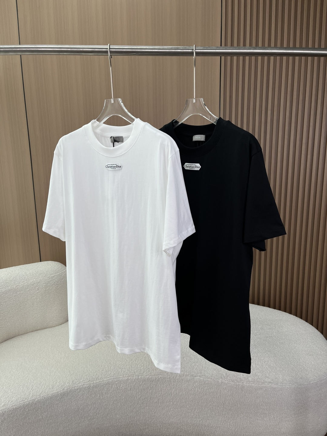 NO:834365,Dior hexagon logo cotton T-shirt!  1. Visual core: The hexagonal patch logo is used in the center of the chest, with the words 'Christian Dior PARIS' engraved on it. The font is neat and clear, and the edge of the patch is delicately seamed. It is the most recognizable design element of the brand. The ribbed round neck design has moderate elasticity, fits the neck and is not easy to deform; the short sleeves are neatly cut, and the dropped shoulder design weakens the shoulder line, making it more casual.  The straight hem and no slits on the sides maintain the overall minimalist feel and are suitable for layering or single wear. 2. Highlights of the craftsmanship: The patch logo is double-fixed by hot pressing and sewing, which is durable and not easy to fall off, and there are no burrs on the edges. The gray Dior collar label is sewn on the inside of the neckline, which has a delicate texture; the wash label is made of silver-grey satin material, with multi-lingual markings on the material and washing instructions. The stitching is fine and even, with no missing stitches or skipped stitches, reflecting the level of Italian handcraftsmanship.  The main fabric is cotton, using high-count combed cotton technology, which is soft to the touch and skin-friendly, has good breathability, good drape, and is not easy to wrinkle.,, dior, dior, T-shirt, tees, t-shirt,19860909迪奥Dior 六边形徽标棉质T恤！ 1. 视觉核心 胸口正中央采用六边形贴布徽标,印刻「Christian Dior PARIS」字样,字体工整清晰,贴布边缘锁边细腻,是品牌辨识度最高的设计元素. 罗纹圆领设计,弹力适中,贴合颈部且不易变形；短袖剪裁利落,落肩设计弱化肩部线条,更显随性. 平直下摆,侧边无开衩,保持整体极简感,适配叠穿或单穿. 2. 工艺亮点 贴布徽标采用热压+车缝双重固定,耐洗不易脱落,边缘无毛刺. 领口内侧缝有灰色Dior领标,质感细腻；洗标为银灰色缎面材质,多语言标注材质与洗涤说明. 缝线细密均匀,无漏针、跳针现象,体现意大利手工工艺水准. 主体面料棉,采用高支精梳棉工艺,触感柔软亲肤,透气性佳,垂感良好,不易起皱.,,dior,dior,T-shirt,tees，t-shirt,,Women's clothing
