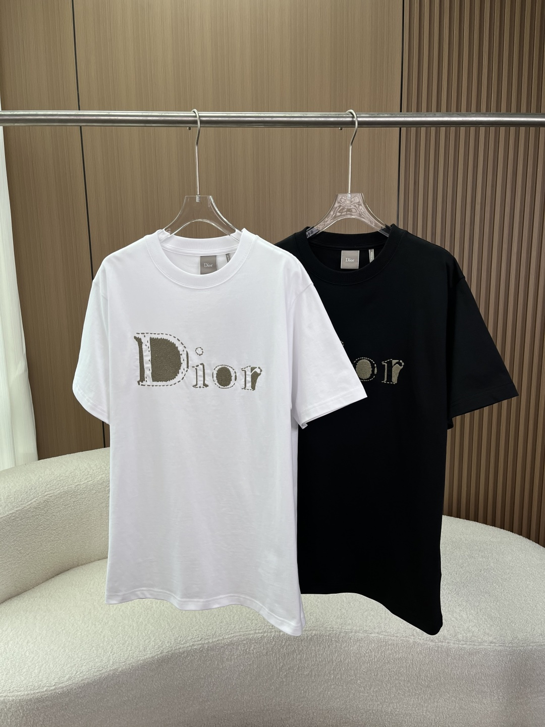NO:833850,(Original customization) Dior Dior 2026 Spring and Summer Reverse Embroidered T-shirt Design Concept and Visual Details Dior Reverse Embroidery The letters on the chest adopt reverse visual embroidery technology, and the edges of the letters are outlined with dotted stitches to simulate the hand-stitching effect. The main body is olive green/khaki flocking texture, forming a 'three-dimensional relief' visual hierarchy. The jagged edge of the letter 'D' contrasts with the rounded font of 'ior'. Style tailoring  The loose, dropped-shoulder version, longer length, and expanded shoulder lines create a lazy and casual street feel, suitable for both men and women. The ribbed round neck uses two-needle topstitching technology to prevent the neckline from deforming and fits the neck without being tight. The color scheme is white and black, and the embroidery is olive green, which highlights the brand recognition in a low-key manner. Fabrics and craftsmanship  The main fabric is cotton jersey imported from Italy, which is soft and skin-friendly, has good breathability, and is not prone to pilling and deformation after washing. The embroidery material is polyester fiber, and the flocking effect is achieved through the jacquard + shearing process. The edge stitches are fine and there are no jumps or missing stitches. Production process The embroidery of each T-shirt needs to go through 12 processes, including pattern making, embroidery, shearing, shaping, etc., to ensure the flatness and three-dimensionality of the pattern.  Wearing suggestions: It is recommended to choose the normal size or one size larger to create an oversize effect; it can be worn alone or layered with suits and denim jackets, suitable for daily commuting, street wear and other scenarios.,, dior, dior, versace, jackets & coats, tees, t-shirt, business suit,19860909（原版定制） 迪奥Dior 2026春夏 Reverse刺绣T恤 设计理念与视觉细节 Dior Reverse刺绣 胸前字母采用反向视觉刺绣工艺,字母边缘以虚线针脚勾勒,模拟手工缝线效果,主体为橄榄绿/卡其色植绒质感,形成“立体浮雕”视觉层次. 字母“D”的锯齿边缘与“ior”的圆润字体形成对比. 版型剪裁 宽松落肩版型,衣长偏长,肩线外扩,营造慵懒随性的街头感,适配男女同款穿搭. 罗纹圆领采用二本针明线工艺,领口不易变形,贴合颈部但不紧绷. 配色方案 白色与黑色两种基础色,刺绣别为橄榄绿,低调中凸显品牌辨识度. 面料与工艺 主体面料意大利进口棉质平纹针织,触感柔软亲肤,透气性佳,洗后不易起球变形. 刺绣材质刺绣部分为聚酯纤维,通过提花+剪毛工艺实现植绒效果,边缘针脚细密,无跳线、漏针. 生产工艺每一件T恤的刺绣需经过12道工序,包括打版、刺绣、剪毛、定型等,确保图案平整度与立体感. 穿着建议建议选择正常尺码或偏大一码,打造oversize效果；可单穿或叠搭西装、牛仔外套,适配日常通勤、街头穿搭等多种场景.,,dior,dior,versace,jackets & coats,tees，t-shirt,business suit,,Women's clothing