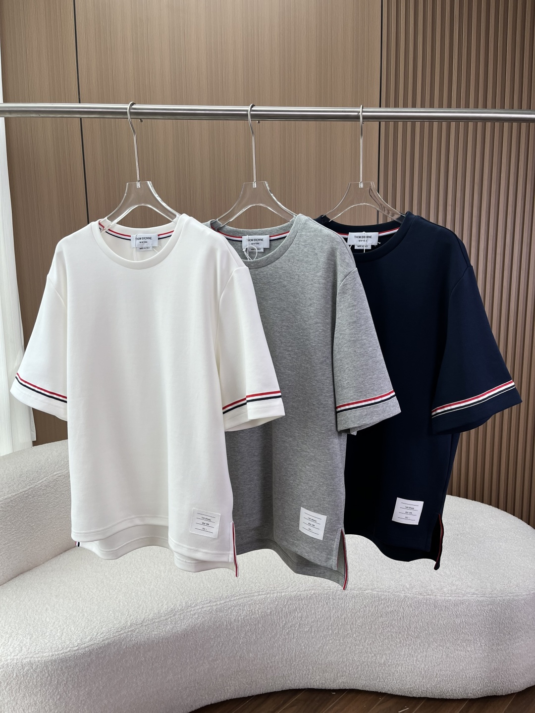 NO:902512,Thom Browne classic round neck short-sleeved T-shirt!  This is Thom Browne's classic round-neck short-sleeved T-shirt, available in three basic colors: white, navy blue, and heather gray. It is an evergreen item of the brand and an entry-level iconic garment. 1. Fabric and Material Ingredients: Cotton, made of high-count combed plain cotton. It has the advantages of being soft and skin-friendly, breathable and sweat-absorbent, and has a crisp and stylish texture that is not easy to collapse or deform. It is comfortable to wear in summer and does not make you sweaty.  The process has been pre-shrunk, making it less likely to shrink after multiple washes and keeping the shape stable. 2. Iconic design details This T-shirt completely retains the core identification design of the Thom Browne brand, and every detail carries the brand’s iconic language.  The red, white and blue (RWB) three-color webbing serves as the brand's 'visual identity card'. The three-color webbing is inspired by the American flag. Contrast-colored webbing is used on the inside of the neckline at key locations throughout the entire T-shirt. A circle of webbing decoration surrounds the cuffs. The slits on both sides of the hem are also embellished with webbing details. This not only strengthens the brand recognition, but also makes the basic T-shirt more layered and refined.  The brand's iconic white label is sewn on the right side of the hem with brand specification information printed on it. It is one of Thom Browne's most representative design symbols, adding iconic recognition to the simple body. The side slit hem design has a classic slit cut on both sides of the hem. The slit is also matched with a three-color webbing, which not only increases the margin of body movement and improves wearing comfort, but also continues the brand's iconic tailoring style, making the T-shirt more drapey and stylish when worn.  The reinforced rib round neck is designed with high-elastic reinforced ribs and is matched with a three-color webbing on the inside. It is not easily deformed after repeated washing and the neckline does not collapse. It fits the neck perfectly and extends the service life of the T-shirt. The loose straight version adopts a loose cut with dropped shoulders and straight legs. It is a unisex design for men and women and is not picky about body shapes. It can not only create a relaxed old-money style, college-style wear, but also supports matching for couples, suitable for diverse wear scenarios. 3. Applicable scenarios  For daily casual commuting, shopping, and dating, create a minimalist and high-end look. Light business suits and jackets are suitable for light business scenes in the workplace, taking into account both formality and casualness. Couple wear is designed in the same style for men and women, and can be worn as a couple when going out on the street, making it highly recognizable. Suitable for single wear in summer and inner wear in spring and autumn, one piece covers the needs of multiple seasons.,,jackets & coats, T-shirt, tees, t-shirt, business suit,19860909Thom Browne 经典款圆领短袖T恤 ！ 这是Thom Browne的经典款圆领短袖T恤,白色、藏青色、麻灰色3种基础配色可供选择,是品牌的常青款单品,也是入门级标志性服饰. 1. 面料与材质 成分 棉,采用高支精梳平纹棉 优势柔软亲肤、透气吸汗,同时具备挺括有型的质感,不易软塌、变形,夏季穿着舒适不闷汗. 工艺经过预缩水处理,多次洗涤后不易缩水,保持版型稳定. 2. 标志性设计细节 这件T恤完整保留了Thom Browne品牌最核心的识别设计,每一处细节都承载着品牌的标志性语言 红白蓝（RWB）三色织带作为品牌的「视觉身份证」,三色织带灵感源自美国国旗,贯穿整件T恤的关键位置领口内侧做撞色织带包边,袖口处环绕一圈织带装饰,下摆两侧的开叉处也点缀织带细节,既强化了品牌辨识度,也让基础款T恤更有层次与精致感. 白色品牌标贴在下摆右侧缝制了品牌标志性的白色标贴,印有品牌规格信息,是Thom Browne最具代表性的设计符号之一,为简约的衣身增添了标志性的识别度. 侧开叉下摆设计下摆两侧做了经典的开叉剪裁,开叉处同样搭配三色织带,既增加了肢体活动的余量,提升穿着舒适度,也延续了品牌标志性的剪裁风格,让T恤在穿搭时更有垂坠感和造型感. 加固罗纹圆领领口采用高弹加固罗纹设计,搭配内侧的三色织带,多次洗涤后不易变形、领口不垮塌,完美贴合颈部,同时延长了T恤的使用寿命. 宽松直筒版型采用落肩+直筒的宽松剪裁,男女同款的中性设计,不挑身材,既能打造松弛感的老钱风、学院风穿搭,也支持情侣款搭配,适配多元穿搭场景. 3. 适用场景 日常休闲通勤、逛街、约会,打造极简高级感穿搭. 轻商务内搭西装、夹克,适配职场轻商务场景,兼顾正式与休闲. 情侣穿搭男女同款设计,可作为情侣款出街,辨识度拉满. 四季适配夏季单穿,春秋内搭,一件覆盖多季节穿搭需求.,,jackets & coats,T-shirt,tees，t-shirt,business suit,,Women's clothing