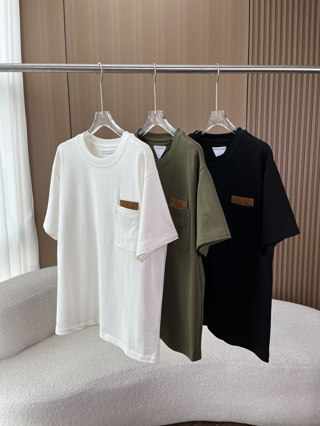 NO:808349,(With real cowhide) Bottega Veneta BV woven leather label pocket T-shirt!  1. Brand Soul Design The hand-woven leather label on the chest pocket is the iconic Intrecciato leather weaving process of BV. Without exaggerating the logo, this delicate rhombus weaving texture alone can convey low-key and luxurious brand recognition, which perfectly fits the brand's design philosophy of 'no logo is better than having a logo'. 2. Fabric and pattern  Made of high-count combed cotton fabric, it feels soft and skin-friendly, has strong breathability, and will not make you sweaty when worn in summer. The oversize version with loose shoulders is very tolerant to the body, and the upper body has a relaxed and high-end feel. It can be worn alone or layered to create a simple and advanced look. 3. Multi-color and versatile attributes. Available in off-white, military green, and classic black, suitable for various wearing scenarios. Off-white is gentle and clean, suitable for casual and light business styles.  Military green has a retro texture and is suitable for work wear and street wear. Black is versatile and is a universal basic style in the wardrobe, bottega veneta, bottega veneta, versace, bottega veneta, tees, t-shirt, cowhide,19860909（配真牛皮） 葆蝶家（Bottega Veneta）BV编织皮标口袋T恤！ 1. 品牌灵魂设计 胸口口袋处的手工编织皮标,正是BV标志性的Intrecciato皮革编织工艺.不用夸张logo,仅靠这种细腻的菱格编织纹理,就能传递低调奢华的品牌辨识度,完美契合品牌“无logo胜有logo”的设计哲学. 2. 面料与版型 采用高支精梳棉面料,手感软糯亲肤,透气性强,夏天穿着不闷汗.宽松落肩的Oversize版型,对身材包容性极强,上身自带松弛高级感,单穿、内搭都能打造简约高级的造型. 3. 多色百搭属性 提供米白、军绿、经典黑三色可选,适配各种穿搭场景 米白温柔干净,适配休闲、轻商务风 军绿自带复古质感,适配工装、街头穿搭 黑色百搭不出错,是衣橱里的万能基础款,,bottega veneta,bottega veneta,versace,bottega veneta,tees，t-shirt,cowhide,,Women's clothing