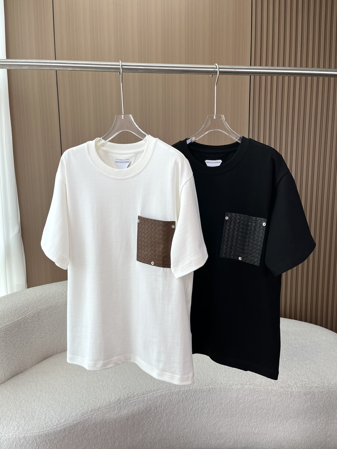 NO:808353,Bottega Veneta (Bottega Veneta) woven pocket T-shirt core design highlights 1. Soul element woven leather pocket This is an extension of BV's iconic Intrecciato leather weaving process. The pocket is hand-woven with diamond leather and fixed with three metal rivets. It is not only a practical pocket, but also the visual focus of the entire garment, low-key highlighting the brand recognition. 2. Simple and versatile basic version  Round neck + loose short-sleeved cut, both black and white are timeless basic colors, suitable for a variety of styles, and the same design for men and women also makes it a popular choice for couples. Materials and process details The main fabric is 100 cotton, high-count heavyweight pure cotton, with a high weight, the upper body is crisp but not soft, skin-friendly, breathable and not easy to deform.  The leather weaving of the pocket craft is handmade, with uniform texture and no obvious jumpers or misalignments; the metal rivets are customized accessories, which fit the leather and fabric well and have no burrs or oxidation marks.,,bottega veneta,bottega veneta,bottega veneta,T-shirt,tees,t-shirt,19860909Bottega Veneta（葆蝶家）编织口袋T恤 核心设计亮点 1. 灵魂元素编织皮革口袋 这是BV的标志性Intrecciato皮革编织工艺的延伸应用.口袋采用菱格纹皮革手工编织而成,以三颗金属铆钉固定,既是实用口袋,也是整件衣服的视觉焦点,低调地凸显品牌辨识度. 2. 简约百搭的基础版型 圆领+宽松短袖剪裁,黑/白两款都是永不过时的基础色,适配多种穿搭风格,男女同款的设计也让它成为情侣款的热门选择. 材质与工艺细节 主体面料100棉,高支重磅纯棉,克重较高,上身挺括不软塌,亲肤透气且不易变形. 口袋工艺皮革编织为手工制作,纹理均匀,无明显跳线或错位；金属铆钉为定制配件,与皮革、面料的贴合度高,无毛刺或氧化痕迹.,,bottega veneta,bottega veneta,bottega veneta,T-shirt,tees，t-shirt,,Women's clothing