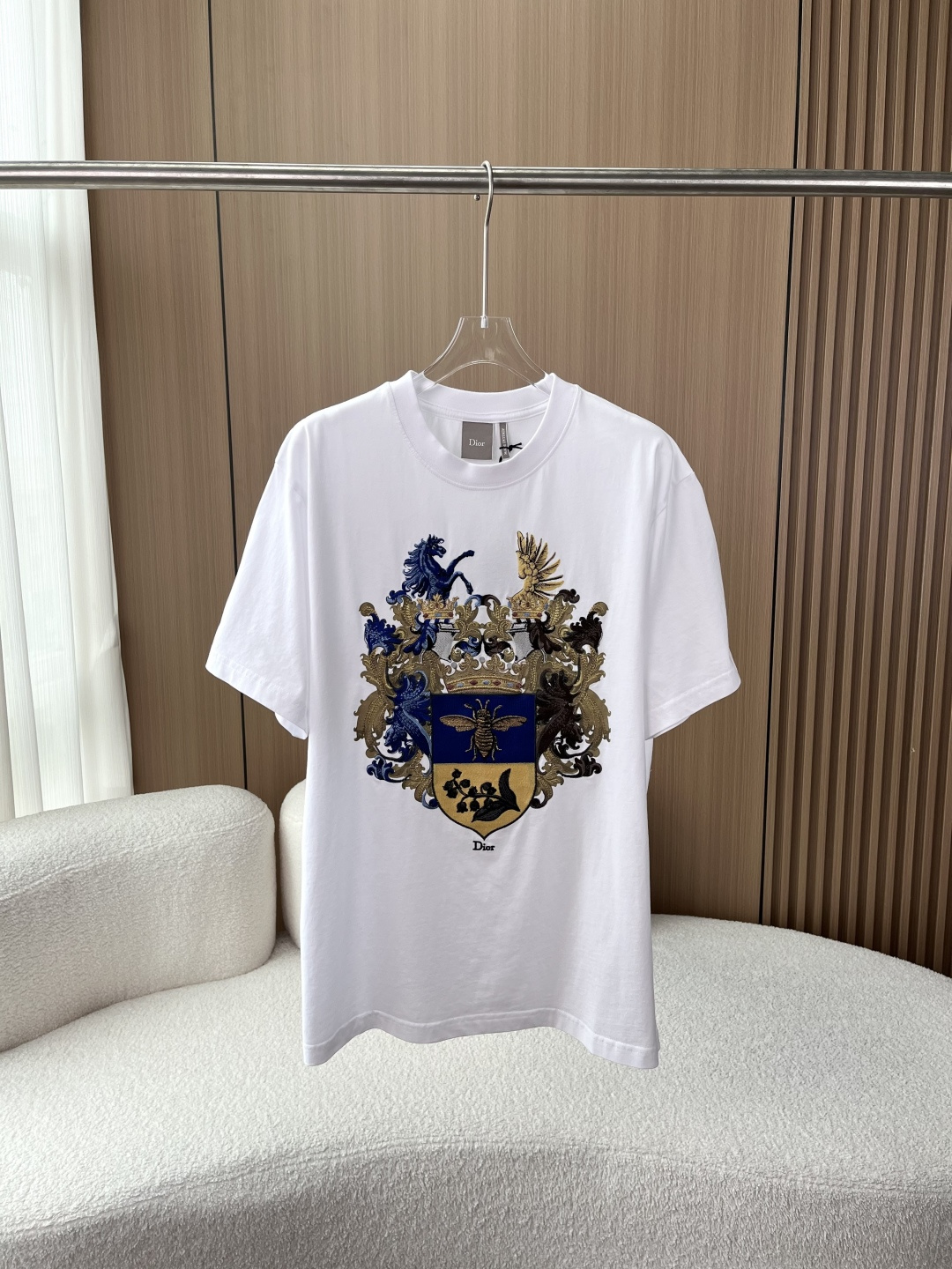 NO:830296,(Original version purchased for customization) DIOR Dior badge embroidered white T!  Wear the royal emblem on your body, a private collection of high-end luxury players, a god-like aristocratic quality. The soul of this T-shirt is the heavy-duty royal embroidery on the chest, which perfectly combines DIOR’s classic bee elements with the aesthetics of European aristocratic heraldry. In the coat of arms, the bee embroidery in contrasting blue and gold colors is outlined with metal threads, and the luster is directly full, and each tentacle is clearly defined;  The blue and brown horses, curly grass pattern and crown on both sides use more than three kinds of embroidery techniques, with gradient blue, gold and brown threads, embroidering the baroque gorgeousness to the fullest. Looking closely, you can feel the three-dimensional texture of the embroidery, which feels uneven and has no cheap plastic feel at all. Every stitch is hand-made and exquisite.  The fabric is made of high-count combed cotton, which feels soft and crisp. The upper body does not collapse at all and does not cling to the flesh. The white color is not transparent, so it is breathable and does not make you sweaty in summer. The loose-fitting, dropped-shoulder cut is not flattering on your figure. Boys wear it with a sense of relaxation. Girls can also wear it casually with a boyfriend style, easily hiding their belly and wide shoulder line.  The detail control is ecstatic. The neckline has thickened and reinforced threads, which will not deform after long-term wear. The stitching is so neat that even obsessive-compulsive disorder can't fault it. The embroidery on the inside is also hemmed so that it does not prick the skin at all. It doesn't take a lot of effort to match, and it looks elegant in any casual wear. Pair it with straight jeans and leather shoes, which will give you the relaxed feeling of a noble man when you go out on the street. Pair it with a linen suit, and you can wear it with a low-key luxury taste even when commuting to work.  Paired with shorts and sneakers, you can wear it effortlessly on the weekends with a sense of fashion., dior, dior, shorts, jeans, tees, t-shirt, business suit,19860909（原版入手定制） DIOR迪奥徽章刺绣白T！ 把皇室纹章穿在身上 高奢玩家私藏款,一件封神的贵族级质 这件T恤的灵魂,就是胸前这枚重工皇室纹章刺绣,把DIOR的经典蜜蜂元素和欧洲贵族纹章美学完美融合. 盾形纹章里,蓝金撞色的蜜蜂刺绣用金属线勾勒,光泽感直接拉满,每根触角都根根分明； 两侧的蓝棕骏马、卷草纹与皇冠,用了3种以上的刺绣工艺,深浅渐变的蓝、金、棕三色线,把巴洛克的华丽感绣得淋漓尽致； 近看能感受到刺绣的立体肌理,摸上去凹凸有致,完全没有廉价的塑料感,每一针都是手工级的精致. 面料高支精梳棉,手感软糯又挺括,上身完全不塌不贴肉,白色也不透肉,夏天穿透气不闷汗； 版型宽松落肩剪裁,不挑身材,男生穿自带松弛感,女生穿也能穿出男友风的随性,轻松藏住小肚腩和宽肩线； 细节控狂喜领口做了加厚加固的螺纹,久穿也不会变形,走线工整到强迫症都挑不出毛病,内里的刺绣也做了包边处理,完全不扎皮肤. 不用费脑搭配,随便穿都显贵 搭配直筒牛仔裤+皮鞋,就是贵公子出街的松弛感； 外搭一件亚麻西装,上班通勤也能穿出低调的高奢品味； 配短裤+板鞋,周末出门也能穿出不费力的潮流感.,,dior,dior,shorts,jeans,tees，t-shirt,business suit,,Women's clothing