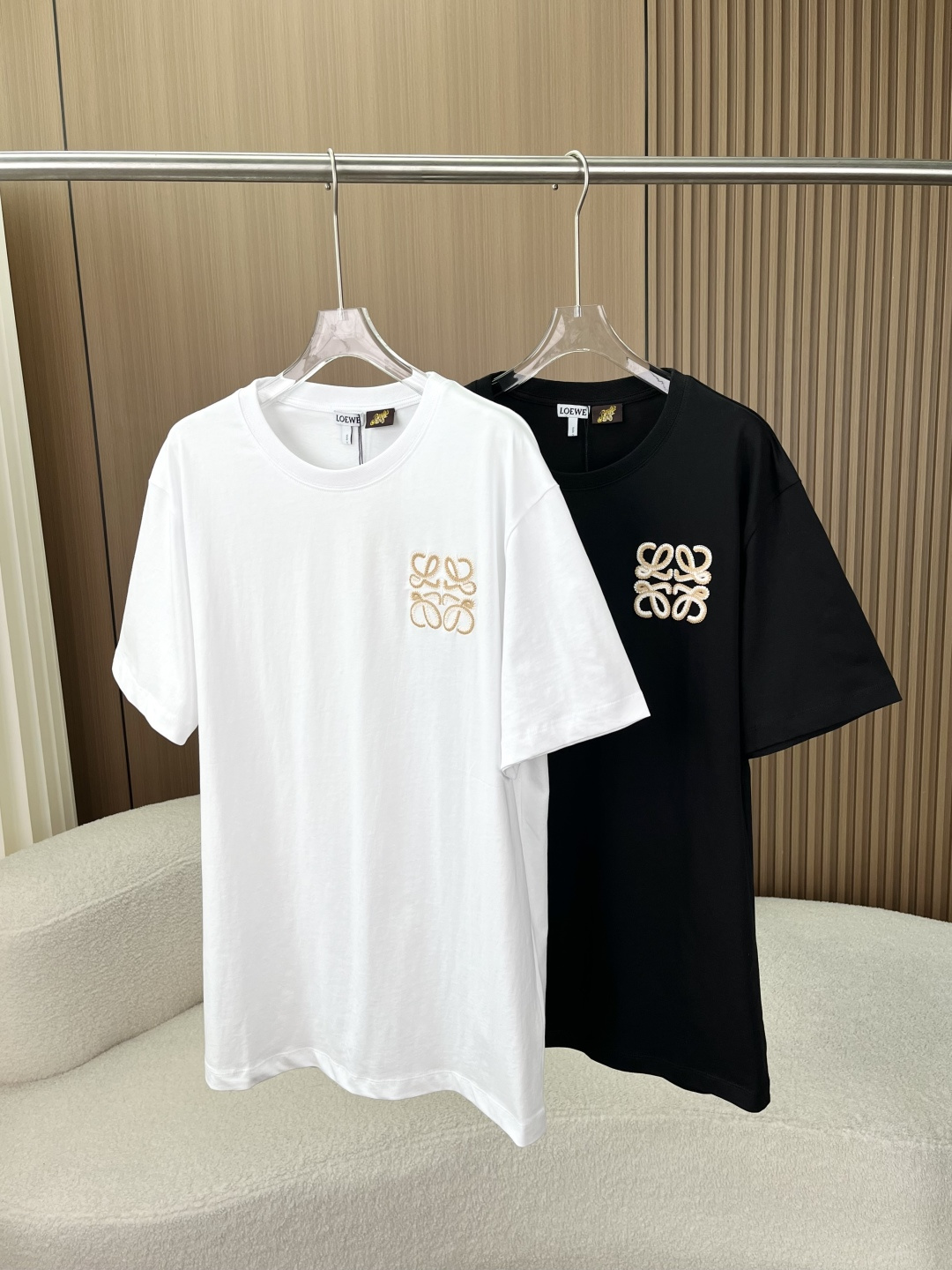 NO:841700,(Original customization) Loewe classic Anagram two-color embroidered T-shirt. High-count cotton silhouette short-sleeved. Same style for men and women in black and white. Bring Spanish artistic relaxation into daily life. Unobtrusive totem is the high-end secret code that only those who understand can get [Brand DNA · Two-color embroidery details control ecstasy]  The brand's iconic Anagram totem is restored on the chest, using beige + white double hook embroidery technology with thousands of needles. The stitches are full and three-dimensional, and the seams are neat and dense. There are no excess threads, and repeated machine washing will not cause fuzzing. The low-key small logo design is not exaggerated or ostentatious. Say goodbye to the big logo models that are popular on the street. The sense of luxury is hidden in the details, and the upper body has 'effortless nobility'. [Fabric texture · Soft but not collapsed cabinet-level experience]  Selected high-count and high-density double-ply cotton fabric (compared to standard cabinet-level technology), it feels soft and skin-friendly, but the upper body has its own stiffness, which is not soft and close to the flesh at all, and will not become loose and deformed after long-term wear. It is breathable and non-stuffy, and it is refreshing and non-sticky in summer. There is no foreign body feeling when worn next to the skin. It remains flat after washing and is not easy to pill, making daily wear comfortable and worry-free. [Detail-controlled craftsmanship ·  Every part can withstand magnification] Reinforced threaded neckline, high elastic thread + double stitching and three-needle technology, it will not loosen and deform after long-term wear and washing, saying goodbye to the embarrassment of 'wearing it twice and collapsing into a straight collar'. Precision hemming stitching shoulder line, cuffs, and hem are neatly double-threaded, with even and smooth routing, no excess thread, and quality can be seen in the details.  The slightly loose silhouette is a drop-shoulder version that doesn't flatter your figure. Boys can wear it neatly and loosely, while girls can wear it in a lazy and casual way. It's friendly to all body shapes [Wearing scenarios · Covering all styles of daily life] Black and white are versatile and necessary colors in the wardrobe, and can be easily worn alone or layered, loewe, loewe, T-shirt, tees, t-shirt,19860909（原版定制） Loewe罗意威经典Anagram双色刺绣T恤 高支棉廓形短袖 男女同款黑白两色 把西班牙的艺术松弛感,穿进日常里 不张扬的图腾,才是懂的人才能get的高级暗号【品牌基因 · 双色刺绣细节控狂喜】 胸前还原品牌标志性Anagram图腾,采用米色+白色双勾边万针刺绣工艺,线迹饱满立体,锁边工整密实,没有多余线头,反复机洗也不会脱线起毛. 低调的小标设计,不浮夸不张扬,告别烂大街的大logo款,把高级感藏在细节里,上身自带“不费力的贵气”.【面料质感 · 软而不塌的柜级体验】 甄选高支高密双股棉面料（对标柜级工艺）,摸起来是软糯亲肤的触感,上身却自带挺括度,完全不会软塌贴肉,久穿也不会松垮变形. 透气不闷汗的特性,夏天穿清爽不黏身,贴肤穿也毫无异物感,洗后依然保持平整,不易起球,日常穿舒适又省心.【细节控的匠心工艺 · 每一处都经得起放大】 加固螺纹领口高弹力螺纹+双车线三本针工艺,久穿久洗也不会松垮变形,告别“穿两次就垮成一字领”的尴尬 精密包边锁缝肩线、袖口、下摆都做了工整的双线包边处理,走线均匀流畅,没有多余线头,细节处见品质 微宽松廓形不挑身材的落肩版型,男生穿利落松弛,女生穿慵懒随性,对各种身形都友好【穿搭场景 · 承包全风格的日常】 黑白两色都是衣柜里的百搭刚需色,单穿叠穿都能轻松驾驭,,loewe,loewe,T-shirt,tees，t-shirt,,Women's clothing