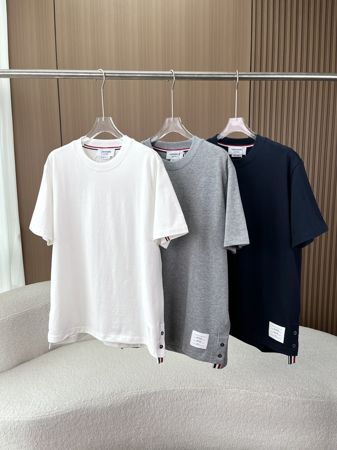 NO:836414,Thom Browne's classic TB four-stripe web short-sleeved T-shirt - Wear classics into a style that never goes out of style. The brand's iconic design is instantly recognizable. The red, white and blue webbing running through the inside of the collar and back is TB's most recognizable DNA design, low-key and memorable. The shell buckle + webbing slit on the side of the hem, paired with the brand's cloth logo, are recognizable in every detail, unobtrusive but understood by everyone who knows it. Heavy high-count cotton, soft and crisp  Selected high-count combed cotton fabric, the upper body is soft and skin-friendly, and has a sinewy feel, not soft or fleshy. After pre-shrinking, it will not be easily deformed or balled after washing, and it can maintain a new texture even if it is worn for a long time. It is a basic style that can be worn in the wardrobe for many years. The craftsmanship of controlling the fullness of the details. Three needles to reinforce the neckline, not easy to loosen and deform after long-term wear, and fit the neck line without blocking the neck.  Shell buckles + webbing slits, neat routing, and factory craftsmanship in every detail. Slightly loose fit, not picky on body shape, easy to hide the flesh, boys and girls can wear it with a casual and relaxed feeling. Three colors are available, close your eyes and avoid stepping on thunder. Classic white is clean and refreshing, suitable for pairing with jeans and trousers, the king of all-match in spring and summer. Heather gray comes with advanced filters, with a sense of relaxation, suitable for commuting and leisure.  Navy blue is calm and elegant, with a low-key elegance, and can be easily adapted to business situations. The dressing formula is copied directly. Pair it with drapey trousers + white shoes, and you will become an urban elite with a sense of relaxation; pair it with casual shorts + sneakers, and you will become a casual and classy street trend in an instant. One piece can unlock N kinds of styles.,,shorts,jeans,T-shirt,tees,t-shirt,19860909Thom Browne 经典款TB四条纹织带短袖T恤 ——把经典穿成永不落伍的风格 一眼识标的品牌标志性设计 领口内侧、背部贯穿的红白蓝织带,是TB最具辨识度的DNA设计,低调又有记忆点. 下摆侧边的贝壳扣+织带开叉,搭配品牌布标,细节里都是辨识度,不张扬却懂的人都懂. 重磅高支棉,软糯又挺括 甄选高支精梳棉面料,上身软糯亲肤,同时自带筋骨感,不软塌、不透肉. 经过预缩水处理,洗后不易变形、不起球,久穿也能保持如新的质感,是衣柜里能穿很多年的基础款. 细节控拉满的工艺 三本针加固领口,久穿不易松垮变形,贴合颈部线条不卡脖子 贝壳扣+织带开叉,走线工整利落,细节里都是大厂工艺 微宽松的版型,不挑身材,轻松藏肉,男生女生都能穿出随性松弛感 三色可选,闭眼入不踩雷 经典白干净清爽,搭配牛仔裤、西裤都很适配,春夏的百搭王者 麻灰色自带高级滤镜,自带松弛感,通勤休闲都能hold住 藏青色沉稳大气,自带低调贵气,商务场合也能轻松适配 穿搭公式直接抄 搭配垂感西裤+小白鞋,就是自带松弛感的都市精英；搭配休闲短裤+板鞋,秒变随性又有品的街头潮人,一件解锁N种风格.,,shorts,jeans,T-shirt,tees，t-shirt,,Women's clothing