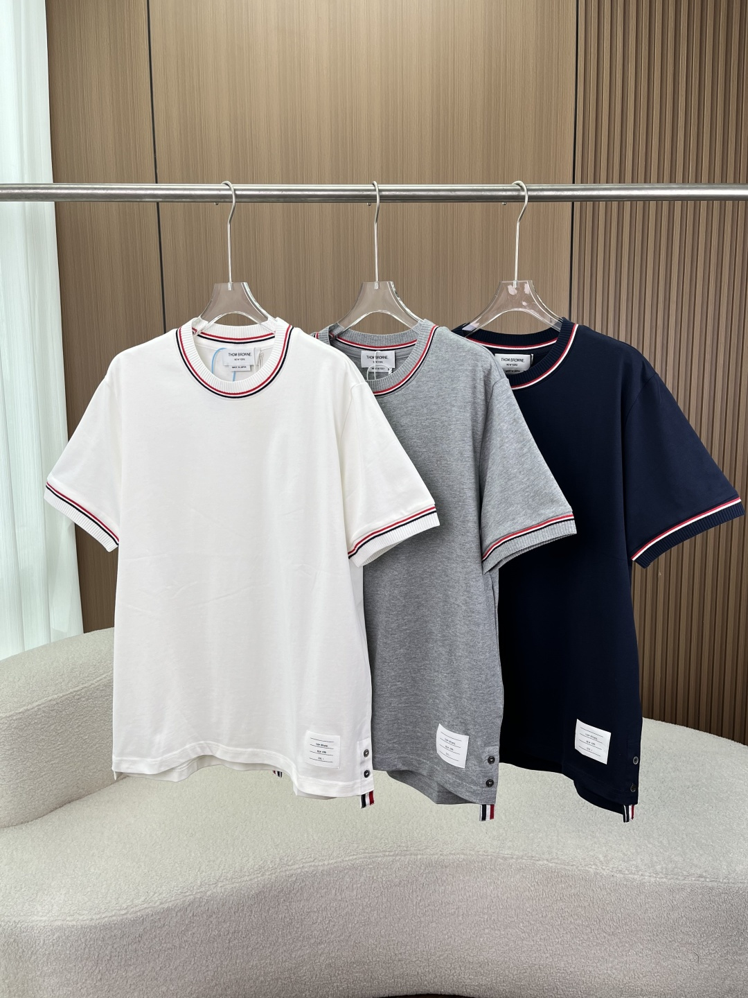 NO:908512,(High quality) Thom Browne classic contrast striped short-sleeved T-shirt. TB is a timeless college-style item that can easily achieve a high-end casual feel. The brand's iconic design of the red, white and blue webbing on the collar and cuffs is Thom Browne's classic logo. The iconic woven label and shell buckle details on the side of the hem low-key highlight the brand recognition and have a high-end texture.  The comfortable and skin-friendly fabric is made of high-count pure cotton, which is soft and delicate to the touch. It is breathable and sweat-absorbent without being stuffy. The upper body is skin-friendly and does not tie the body. It combines comfort and texture and can be worn in all seasons. The neatly tailored version is a classic straight version, loose and not flattering on the figure. The hem design is short in the front and long in the back with side slits, which not only modifies the figure but also adds a sense of layering. It is very stylish when worn alone or layered.  Multi-color options: versatile white, gray, and navy blue. The basic color is suitable for various styles. It can be easily worn with jeans, casual pants, or suit pants. It is a versatile item in the wardrobe. This Thom Browne short-sleeved T-shirt perfectly integrates the brand's iconic elements with daily wear. Whether it is daily commuting, travel, or casual occasions, it can easily wear a simple and high-end college style atmosphere, and can easily take over your summer outfit~,,jeans,T-shirt,tees,t-shirt,business  suit,19860909（高品质） Thom Browne 经典撞色条纹短袖T恤 TB永不过时的学院风单品,轻松拿捏高级休闲感 品牌标志性设计领口、袖口的红白蓝三色织带是Thom Browne的经典标识,下摆侧边的标志性织标与贝壳扣细节,低调彰显品牌辨识度,自带高级质感. 舒适亲肤面料采用高支纯棉面料,触感柔软细腻,透气吸汗不闷热,上身亲肤不扎身,兼顾舒适与质感,四季都能穿. 利落剪裁版型经典直筒版型,宽松不挑身材,前短后长的下摆设计搭配侧边开叉,修饰身形的同时更具层次感,单穿、叠穿都很有型. 多色可选百搭白、灰、藏青三色可选,基础色系适配各种穿搭风格,搭配牛仔裤、休闲裤或西装裤都能轻松驾驭,是衣柜里的百搭刚需款. 这款Thom Browne短袖T恤,把品牌标志性元素与日常穿搭完美融合,无论是日常通勤、出游还是休闲场合,都能轻松穿出简约又高级的学院风氛围,轻松承包你的夏日穿搭~,,jeans,T-shirt,tees，t-shirt,business suit,,Women's clothing