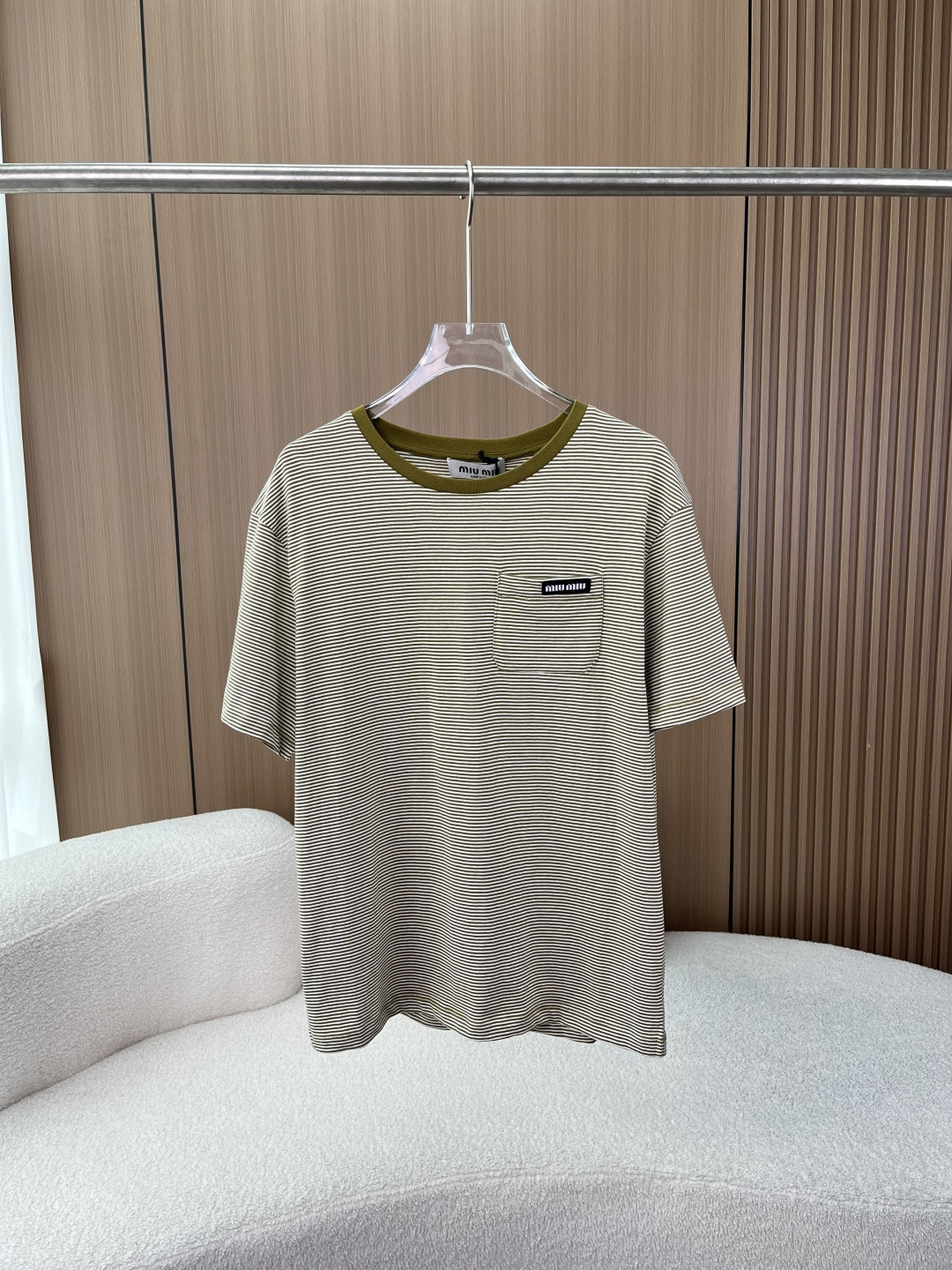 NO:845525,(Original customized fabric) miu miu Miu Miu retro striped short-sleeved T-shirt!  The classic contrasting stripe design brings a French sense of relaxation to the body~ The miu miu woven label on the chest pocket of the brand's iconic design is the finishing touch. It is low-key and highlights the brand's texture. It is easy to identify and does not appear to be deliberately ostentatious for daily wear. The retro contrasting stripes of olive green and off-white pinstripes are paired with the same color contrasting round collar. It has a retro college style atmosphere, which is both age-reducing and eye-catching. It is very stylish when worn alone or layered.  The comfortable and skin-friendly fabric is made of high-count cotton fabric, which is soft and breathable. It is skin-friendly on the upper body and does not tie the body. The loose version is not flattering on the figure and is friendly to all body shapes. It is suitable for daily commuting and travel. The detailed and textured neckline adopts reinforced rib technology, which is not easy to deform after long-term wear. The wiring is neat and fine, and the hem and cuffs are neatly hemmed, showing the brand quality in every detail. This miu  The miu striped T-shirt is a versatile item in the wardrobe. Whether it is paired with jeans, casual pants or a skirt, it can easily create a relaxed and fashionable atmosphere, and can easily take over your summer outfit~,,miumiu,skirts,jeans,T-shirt,tees,t-shirt,19860909（原版定制面料） miu miu 缪缪复古条纹短袖T恤！ 经典撞色条纹设计,把法式松弛感穿在身上~ 品牌标志性设计胸前口袋的miu miu织标是点睛之笔,低调又能彰显品牌质感,轻松拿捏辨识度,日常穿也不会显得刻意张扬. 复古撞色条纹橄榄绿与米白的细条纹搭配同色系撞色圆领,自带复古学院风氛围,减龄又耐看,单穿、叠穿都很有味道. 舒适亲肤面料采用高支棉面料,触感柔软透气,上身亲肤不扎身,版型宽松不挑身材,对各种身形都很友好,日常通勤、出游穿都合适. 细节质感拉满领口采用加固罗纹工艺,久穿不易变形；走线工整精细,下摆和袖口的包边处理利落,细节处尽显品牌品质. 这款miu miu条纹T恤是衣柜里的百搭刚需款,不管搭配牛仔裤、休闲裤还是半身裙,都能轻松穿出松弛又时髦的氛围感,轻松承包你的夏日穿搭~,,miumiu,skirts,jeans,T-shirt,tees，t-shirt,,Women's clothing