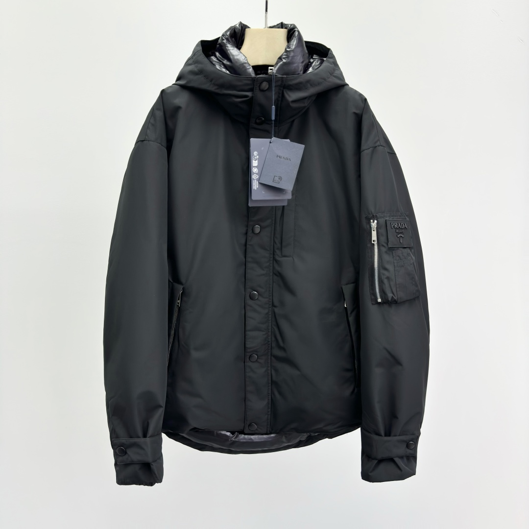 NO:572597,Prad@ Fabric Hooded Down Jacket This modern sporty down jacket is made of fabric and has an Oversize silhouette with a hood. It is filled with warm goose down, combined with practical elements and high-tech details, and presents an innovative and sophisticated style with a minimalist design. To ensure the sustainable care of the product, maintain its properties and reduce its impact on the environment, it is recommended not to wash the product frequently, let it dry naturally after each use, and entrust dry cleaning to a professional environmentally friendly dry cleaner. Oversize version Hood collar Straight sleeves  Zipper and snap fastening Zippered welt pockets Elastic cuffs with straps and snaps Dropped shoulders Rounded back hem Adjustable drawstring Goose down lining and padding Warm-locking seams Logo lettering on sleeves 2832255586,,prada,versace,jackets & coats,down   jacket,hats,alexander wang19860909Prad@ 织物面料连帽羽绒夹克 这款现代运动风羽绒夹克采用织物面料和Oversize宽大廓形,配有风帽.以温暖的鹅绒填充,搭配实用性元素和高科技细节,以极简主义设计呈现创新精致风格. 为确保产品的可持续护理,保持其特性并减少其对环境的影响,建议不要频繁清洗产品,每次使用后让其自然晾干,并委托专业的环保干洗店进行干洗. Oversize版型 风帽衣领 直筒袖 拉链和按扣开合 拉链嵌线袋 弹力袖口配饰带和按扣 落肩 圆弧式背部底边 可调节束绳 鹅绒衬里与填充 锁温接缝 衣袖饰有字母徽标 2832255586,,prada,versace,jackets & coats,down jacket,hats,alexander wang,Men's clothing
