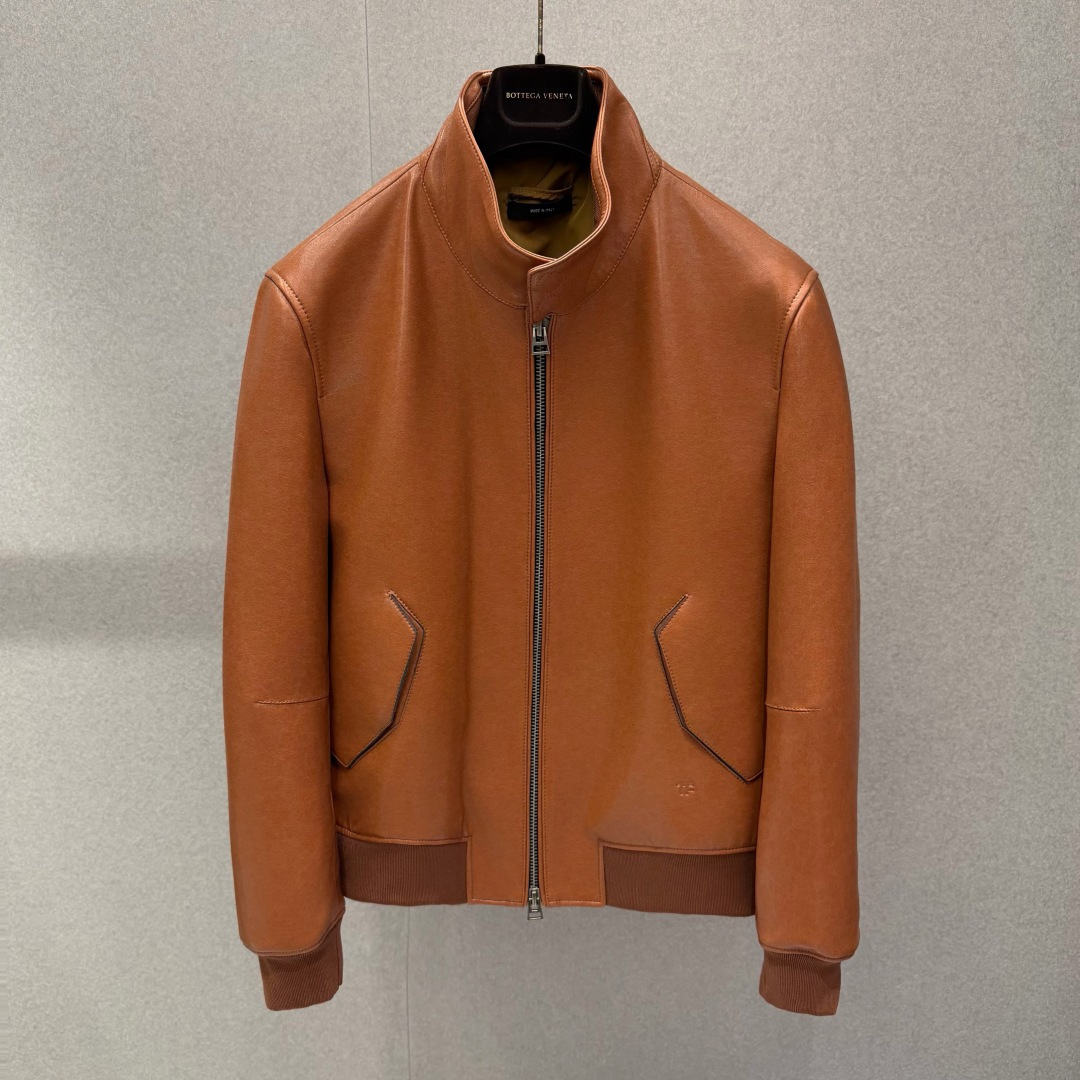 NO:901051,TomF0rd Stand Collar Lambskin Bomber Leather Jacket .00 This bomber jacket combines a retro sports silhouette with top-notch Italian leather craftsmanship. It is made of smooth lambskin that feels as soft as butter. The soft caramel brown tone will naturally fade with wear, giving it a retro texture as it wears.  The improved high stand-up collar design is equipped with two same-leather snap buttons, taking into account windproof effect and neat lines; the central two-way metal zipper runs through the placket, and the beveled welded zipper pockets on both sides are decorated with same-leather snap buttons. The neat dividing line outlines the three-dimensional body. The hem and cuffs are made of dark brown merino wool blend.  The woven ribbing is gathered in, elastic to fit the body shape, locking in temperature while weakening the toughness of the leather. The body is minimalist and has no redundant logos. Only the micro-T metal logo is embossed on the inside of the hem, which is a low-key interpretation of light luxury and restrained texture. It can be worn with shirts and sweaters, and is suitable for commuting, casual, and light formal wear.  Product details and parameters 1. Fabric made of smooth lambskin 2. Ribbed merino wool + cotton blended knit 3. Lined with cotton viscose blend smooth lining to improve the smoothness of putting on and taking off 4. Adjustable collar, two leather buckles at the collar 5. Two-way metal zipper on the placket, matte silver hardware 6. Diagonal zipper pockets on both sides of the pocket, with same-leather snap buttons on the pocket 7.  Standard fit, slightly short cut, optimized upper and lower body proportions 8. Micro-embossed TOM FORD metal logo on the inside of the logo hem 9. Fully hand-cut and sewn in Italy 2842615085, men's clothing, tom ford, jackets & coats, shirts, sheepskin,19860909TomF0rd 立领小羊皮飞行员皮夹克 .00 这件飞行员夹克融合复古运动廓形与意式顶级皮革工艺,甄选触感如黄油般软糯的平滑小羊皮打造,柔和焦糖棕色调随穿着形成自然落色,越穿越有复古质感. 改良高立领设计搭配两颗同皮按扣,兼顾防风效果与利落线条；中央双向金属拉链贯通门襟,两侧斜切嵌线拉链口袋搭配同皮按扣点缀,利落分割线勾勒立体衣身.下摆、袖口采用深棕美利奴羊毛混纺罗纹收束,弹性贴合身形,锁温同时弱化皮革硬朗感.衣身极简无多余标识,仅下摆内侧压印微型T金属logo,低调诠释轻奢内敛质感,可内搭衬衫、针织衫,适配通勤、休闲、轻正装多场景. 产品细节参数 1. 面料平滑小羊皮 2. 罗纹收口美利奴羊毛+棉混纺针织 3. 内衬棉粘混纺顺滑衬里,提升穿脱顺滑度 4. 领型可调节立领,领口两颗皮质包扣 5. 门襟双向金属拉链,哑光银色五金 6. 口袋两侧斜向拉链插袋,袋口配同皮按扣 7. 版型标准合身微短款剪裁,优化上下身比例 8. 标识衣摆内侧微型压印TOM FORD金属logo 9. 意大利全手工裁片缝制 2842615085,男装,tom ford,jackets & coats,shirts,sheepskin,,Women's clothing