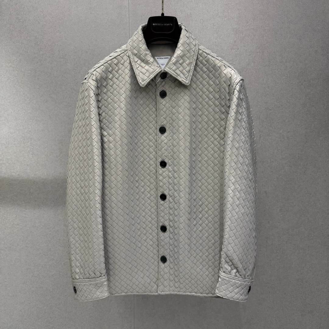 NO:900991,B0ttega Veneta Loose Woven Leather Shirt .00 This loose-fitting shirt is made with the brand's signature Intrecciato hand-weaving process. The entire nappa lambskin strips are interlaced and woven, and the body is covered with a delicate rhombus texture. It is a ready-to-wear expression of BV's ingenious craftsmanship. The soft metallic matte gray gives the leather a matte and delicate luster, weakening the toughness of the leather, and balancing the formal texture with a casual and relaxed atmosphere.  Classic lapel with leather round buttons of the same color, complete button closure at the placket, single-button blouson long sleeves, unlined design to reduce the burden on the upper body, straight and neat hem, it can be worn alone to create a complete suit look, or layered with cashmere high collar, thin knitted layering, suitable for various scenes. Product Details Loose and dropped shoulders, casual fit. Main material: Italian nappa lamb leather, full-width Intrecciato hand-woven  Leather button closure in the same color at the front, single button cinch at the cuffs Unlined lining Straight hem, standard shirt lapels Hand-sewn in Italy 2842616854, Bottega Veneta-Clothing,bottega veneta,bottega veneta,shirts,sheepskin,19860909B0ttega Veneta 宽松编织皮革衬衫 .00 这件宽松版型衬衫以品牌标志性Intrecciato手工编织工艺打造,整片纳帕羔羊皮裁条交错编织,衣身铺满细腻菱格肌理,是BV匠心工艺的成衣表达.柔和金属雾灰赋予皮革哑光细腻光泽,弱化皮革硬朗感,兼顾正装质感与休闲松弛氛围. 经典翻领搭配同色系皮质圆形纽扣,门襟完整纽扣开合,单扣束口长袖,无衬里设计减轻上身负重,衣摆平直利落,既可单穿打造完整套装造型,也可内搭羊绒高领、薄针织叠穿,适配多场景穿搭. 产品细节 版型宽松落肩休闲版型 主料意大利纳帕羔羊皮,全幅Intrecciato手工编织 开合同色皮革纽扣前襟,袖口单颗纽扣收束 内衬无衬里 剪裁平直下摆,标准衬衫翻领 产地意大利纯手工缝制 2842616854,葆蝶家-服装,bottega veneta,bottega veneta,shirts,sheepskin,,Women's clothing