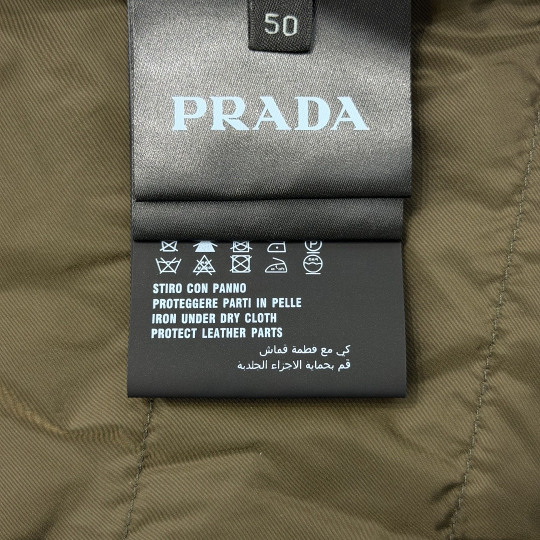 Prad@可卸式束绳兜帽再生尼龙羽绒服外套 这款再生尼龙羽绒外套饰有三角形金属徽标等精美细节,并融科技设计和运动着装元素 Prad@可卸式束绳兜帽再生尼龙羽绒服外套 这款再生尼龙羽绒外套饰有三角形金属徽标等精美细节,并融科技设计和运动着装元素