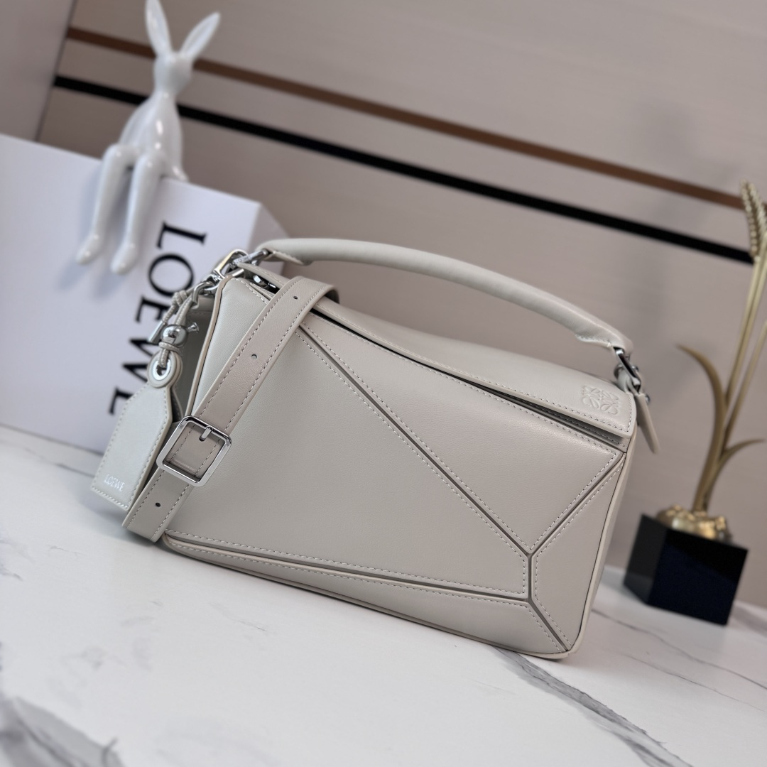 NO:343124,LOw new small Napa sheep leather Featherlight Puzzle handbag outlines rectangular shape with unique geometric lines. Soft and light Napa leather injects casual and lazy style into the handbag. It can be shoulder, crossbody or carry. Removable adjustable shoulder straps with rotary snap zipper opening and closure, articulated zipper head One external zipper rear pocket, one internal insert bag * removable LOE**WE gold or silver label with secret pocket and balloon dice* rectangular metal foot nails Napa sheep leather lining Anagram embossed, decorative internal engraving LOE**WE. Model 062502 size: 24*10.5*16.5cm (with full package), new sheepskin geometric bag, loewe, sheepskin19860909LOw新款 小号纳帕羊皮革 Featherlight Puzzle 手袋 以别具一格的几何线条勾勒长方体造型.柔软轻盈的纳帕皮革为手袋注入随性慵懒的风格.可肩背、斜挎或手提 可拆卸可调节肩带,饰有旋转卡扣*拉链开合,铰接式拉链头 一个外部拉链后袋,一个内部插袋*可拆卸 LOE**WE 烫金或烫银标签,饰有隐秘口袋和气球骰子*长方形金属脚钉 纳帕羊皮革衬里 Anagram 压纹、饰牌内部镌刻 LOE**WE. 型号062502 size:24*10.5*16.5cm（配全套包装）,羊皮新款几何包,loewe,sheepskin,Bag