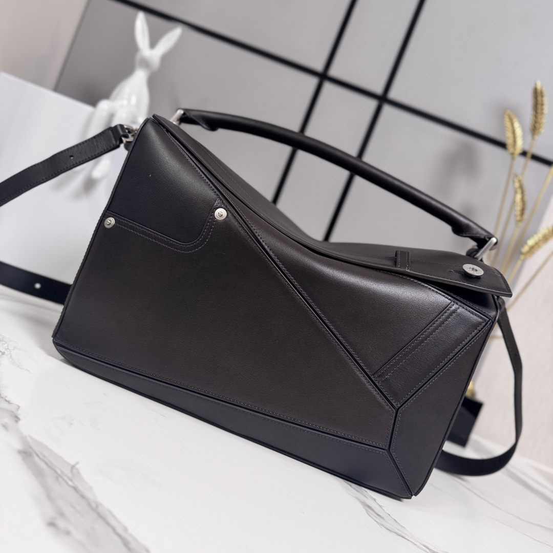 NO:718097,Luojia's new large glossy cow leather Panta Puzzle handbag Puzzle outlines a rectangular shape with unique geometric lines. This large version is made of glossy cowhide and decorated with denim trousers style details. Can be carried on the shoulder, crossbody or handbag*Detachable and adjustable shoulder strap*Zip closure, cowhide zipper pull*One external zippered back pocket, one internal slip pocket Herringbone cotton canvas lining*Anagram embossed  size: 33×14.7×21.5cm model 052500, motorcycle bag (Puzzle Biker), loewe, cowhide19860909罗家新款 大号亮面牛皮革Panta Puzzle 手袋Puzzle 以别具一格的几何线条勾勒长方体造型.此大号版本采用亮面牛皮革制成,饰有单宁布长裤风格细节 .可肩背、斜挎或手提*可拆卸可调节肩带*拉链开合,牛皮革拉链头*一个外部拉链后袋,一个内部插袋人字纹棉质帆布衬里*Anagram 压纹 size: 33×14.7×21.5cm 型号052500,机车包（Puzzle Biker）,loewe,cowhide,Bag