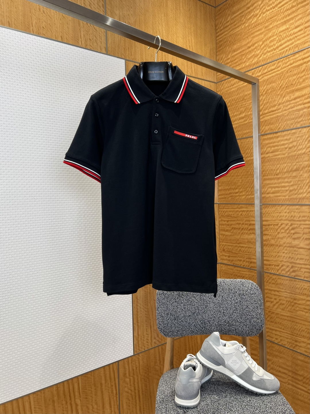 NO:883829,P's Contrast Striped Leather Label Pocket Short Sleeve Polo Shirt  It is made of imported high-count pique cotton fabric, which has been pre-shrunk and anti-pilling. The texture is fine and crisp, soft and skin-friendly. It has good breathability and moisture absorption and perspiration. It is not easy to deform or wrinkle after long-term wear. It perfectly balances the comfort of daily wear and the neatness of business occasions.  ; The neckline adopts a classic lapel design, and the edges are inlaid with red and white contrasting double-striped webbing. The contrasting colors accurately echo the brand's iconic color matching, which not only strengthens the visual recognition, but also outlines a neat neck line; the placket adopts a three-button opening and closing design, and the buttons are made of the same color resin material.  , polished and smooth, fastening smoothly, taking into account both practicality and beauty; a three-dimensional patch pocket is sewn on the left chest, and the edge of the pocket is decorated with a red and white webbing and the brand logo is embossed. The craftsmanship is delicate and neat, which not only enriches the layers of the body but also hides the brand recognition; the cuffs also continue the red and white contrasting double stripe design, which is consistent with  The neckline details echo and the overall vision is coordinated and unified; the version is slightly loose and straight-cut, not flattering on the body shape, which can not only modify the body proportions, but also ensure freedom of movement, and is suitable for daily commuting, leisure travel and other scenarios., Prada-clothing, prada, T-shirt,19860909P家撞色条纹皮标口袋短袖Polo衫 采用进口高支珠地棉面料,经过预缩水处理与抗起球工艺处理,质地细腻挺括,触感柔软亲肤,兼具良好的透气性与吸湿排汗性,久穿不易变形、不易起皱,完美平衡了日常穿着的舒适感与商务场合的利落感；领口采用经典翻领设计,边缘镶嵌红白撞色双条纹织带,色彩对比鲜明,精准呼应品牌标志性配色,既强化了视觉辨识度,又勾勒出利落的颈部线条；门襟处采用三粒纽扣开合设计,纽扣选用同色系树脂材质,打磨光滑,扣合顺畅,兼顾实用性与美观度；左胸位置缝制立体贴袋,袋口边缘饰有红白织带并压印品牌标识,工艺细腻工整,既丰富了衣身层次,又暗藏品牌辨识度；袖口同样延续红白撞色双条纹设计,与领口细节形成呼应,整体视觉协调统一；版型为微宽松直身剪裁,不挑身形,既能修饰身材比例,又保证了活动自由度,适配日常通勤、休闲出行等多种场景.,普拉达-服装,prada,T-shirt,,Women's clothing