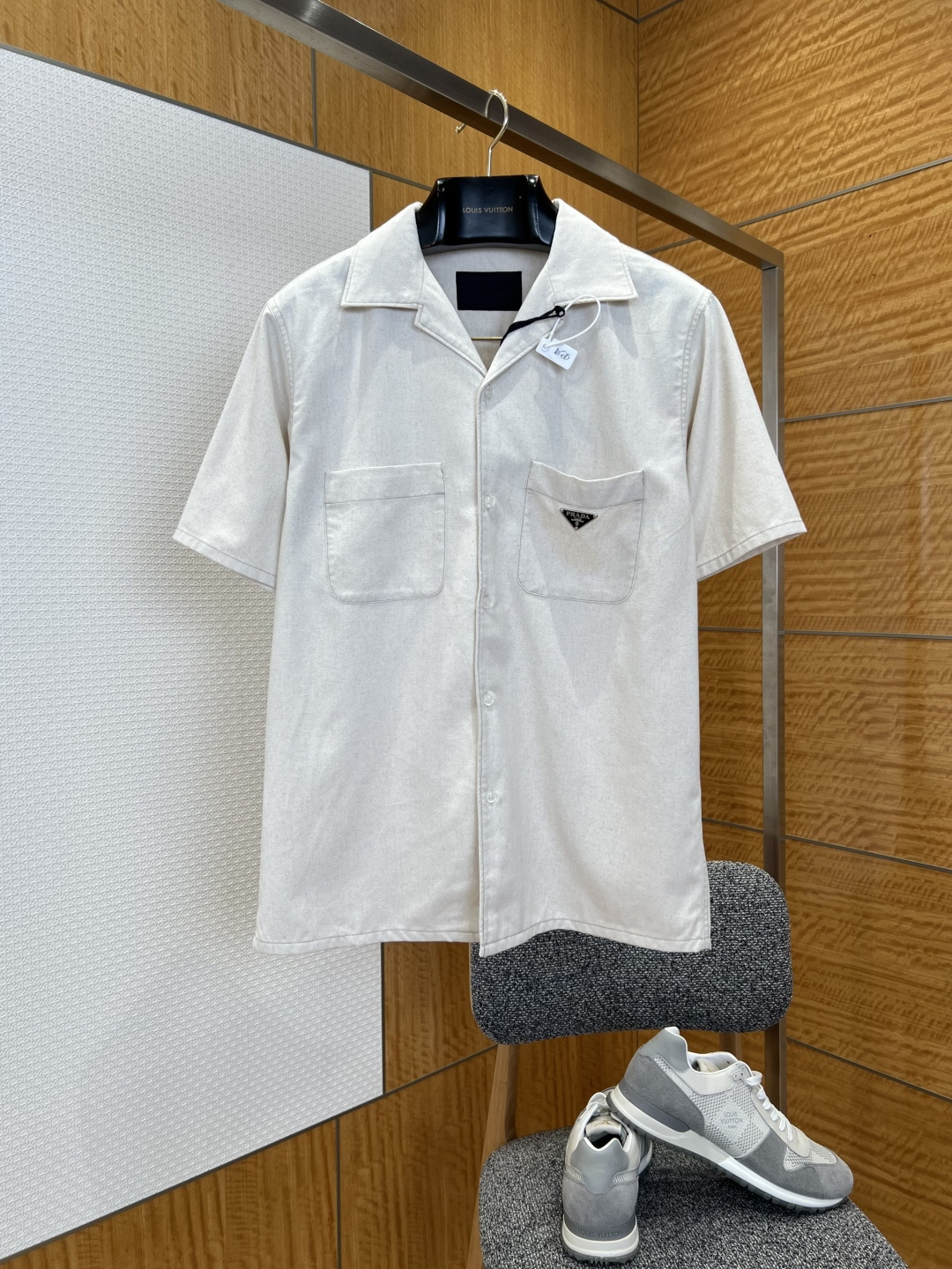 NO:883732,P Home metallic logo two-pocket short-sleeved lapel shirt  It is made of specially imported high-count cotton blended fabric. It has a fine, soft and waxy texture with a crisp and skeletal feel. It feels skin-friendly and comfortable. It has excellent moisture absorption and breathability and good drape recovery. It is not easy to wrinkle and deform after long-term wear, ensuring the quality and practicality of the shirt; the collar is made of  The classic Cuban collar design has an open and natural collar shape, creating a casual yet high-end neck line, which can not only adapt to the daily atmosphere of business and leisure, but also create a lazy and casual vacation feeling; the placket uses natural shell buttons of the same color, with a warm and delicate texture, and the buckle  It is tight and smooth, and every detail highlights the brand's low-key luxury; there are double patch pockets on the front of the body, with a square and full shape and simple and neat lines, adding classic and practical styling details to the simple plain body. The brand's iconic metal triangle logo is exquisitely embellished above the right patch pocket.19860909P家金属徽标双袋短袖翻领衬衫 采用进口特供高支棉混纺面料,质地细腻软糯且自带挺括骨感,触感亲肤舒适,兼具优异的吸湿透气性与良好的垂坠复原性,久穿不易起皱变形,保证了衬衫的品质与实用性；领口采用经典古巴领设计,领型开阔自然,打造出随性又不失高级的颈部线条,既能适配商务休闲的日常氛围,又能营造慵懒随性的度假感觉；门襟选用同色系天然贝壳纽扣,质感温润精致,扣合紧密顺畅,每一处细节都彰显品牌的低调奢华；衣身正面设有双贴袋设计,袋型方正饱满,线条简洁利落,为简约的素色衣身增添经典实用的造型细节,右侧贴袋上方精工点缀品牌标志性金属三角徽标,徽标质感高级醒目,在纯色衣身上形成低调而有力的细节设计点,打破纯色单调感,增添高级辨识度.,普拉达-服装,prada,shirts,T-shirt,,Women's clothing