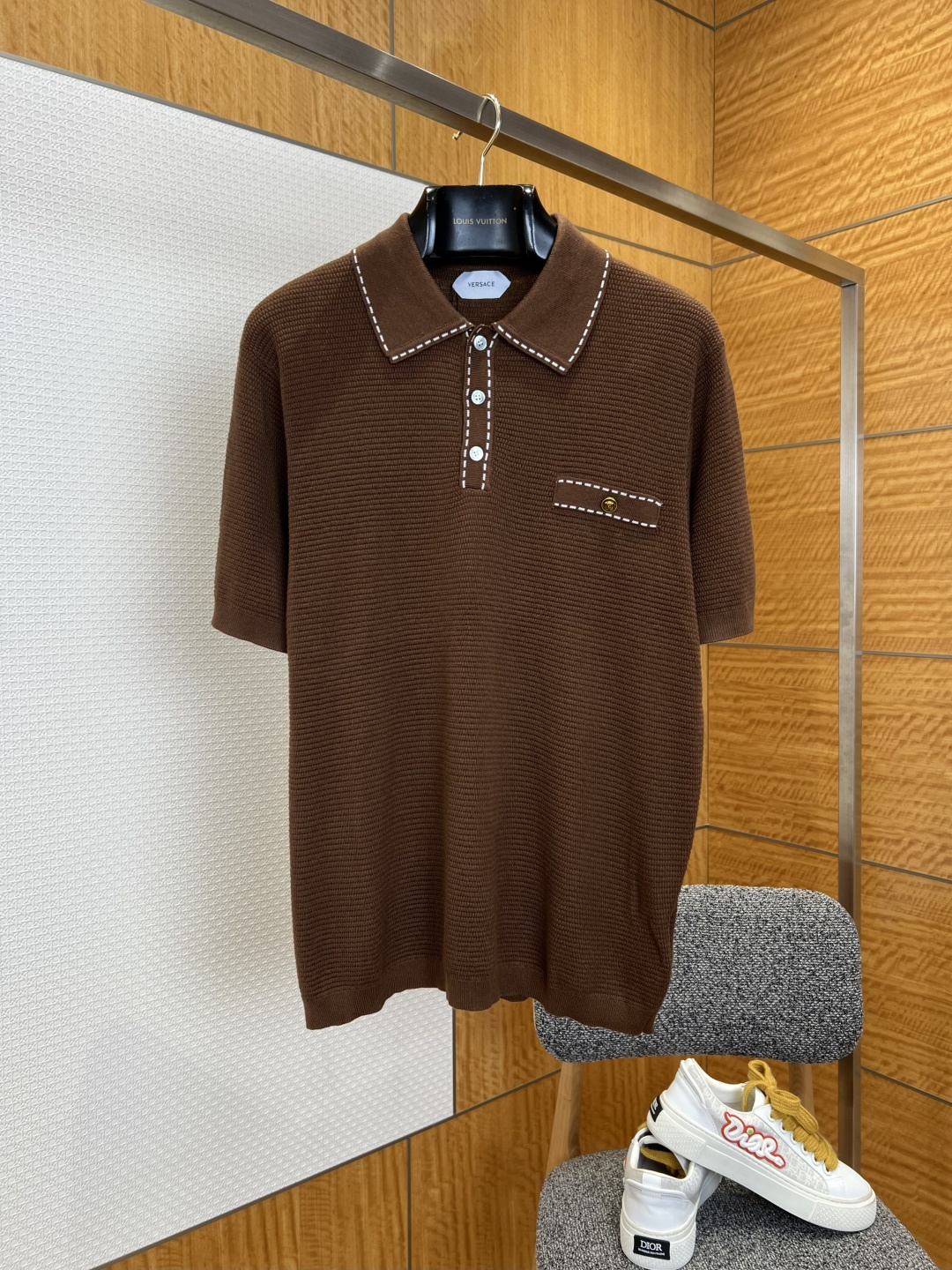 NO:827764,VS open-stitched knitted POLO shirt ————————  Made of customized high-count knitted fabric, the texture is soft and skin-friendly, with a delicate and smooth touch. It has excellent breathability and drape. The upper body is light and pressure-free, and will not easily deform and pill after long-term wear. The body of the garment is made of exquisite waffle texture technology, with a delicate and three-dimensional texture, and a soft and high-end texture that appears under the light.  It gives off a low-key luster; the collar and placket are decorated with contrasting topstitching, the stitching is fine and even, and the stitching is neat and smooth, breaking the monotony of solid colors and adding a sense of retro detailed design; the cuffs and hem are made of plain weave trimming technology, with smooth and neat edges, making it comfortable to wear without being tight; it has a loose and neat fit.  ————————8842088 Material High count knitted fabric Loose fit Color brown/navy blue Size S/M/L/XL, Versace-clothing,versace,19860909VS明线装饰针织POLO衫 ———————— 采用定制高支针织面料,质地软糯亲肤,触感细腻顺滑,兼具出色透气性与垂坠感,上身轻盈无压,久穿不易变形起球；衣身采用精致华夫格织纹工艺,肌理细腻立体,自带柔光高级质感,在光线下呈现出低调的光泽感；领口与门襟采用撞色明线装饰,针脚细密均匀,走线工整流畅,打破纯色单调感,增添复古细节设计感；袖口与下摆采用平纹收边工艺,边缘平整利落,穿着舒适不勒身；宽松利落版型. ————————8842088 材质高支针织面料 版型宽松 颜色棕色/藏青色 尺码S/M/L/XL,范思哲-服装,versace,,Women's clothing