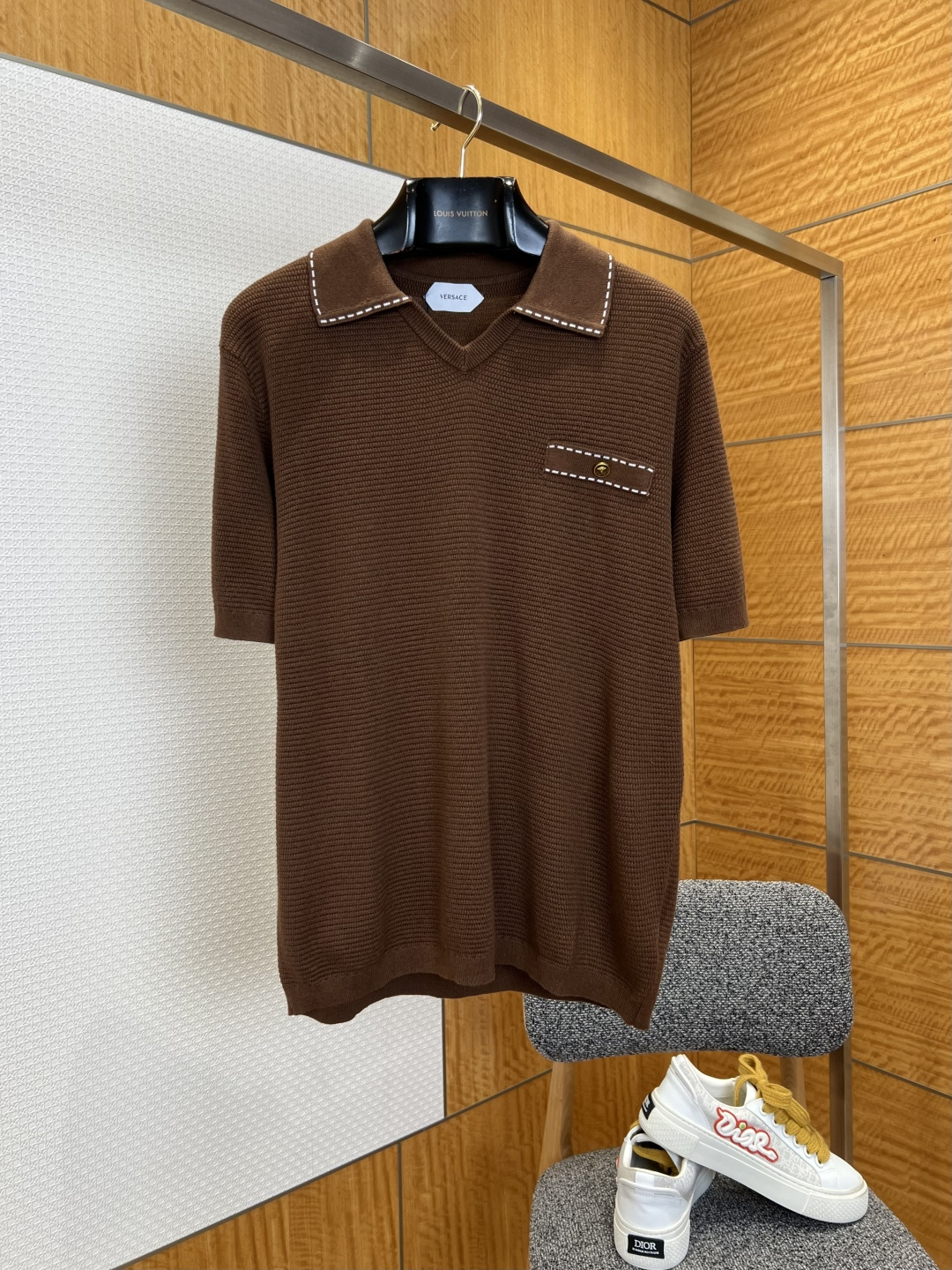 NO:827774,VS topstitched V-neck knitted POLO shirt ————————  Made of customized high-count knitted fabric, the texture is soft and skin-friendly, with a delicate and smooth touch. It has excellent breathability and drape. The upper body is light and pressure-free, and will not easily deform and pill after long-term wear. The body of the garment is made of exquisite waffle texture, with a fine and three-dimensional texture. It has a soft and high-end texture, showing a low-key luster under the light; the collar  The edges of the mouth and left chest pocket are decorated with contrasting topstitching, and the stitching is fine and even, neat and smooth, breaking the monotony of solid colors and adding a sense of retro detail design; the cuffs and hem are made of plain weave edge technology, and the edges are smooth and neat, comfortable to wear without being tight; the loose and neat tailoring is extremely tolerant to various body shapes.  ————————8842088 Material knitted, loose fit, color navy/brown, size S/M/L/XL, Versace-clothing,versace,19860909VS明线装饰V领针织POLO衫 ———————— 采用定制高支针织面料,质地软糯亲肤,触感细腻顺滑,兼具出色透气性与垂坠感,上身轻盈无压,久穿不易变形起球；衣身采用精致华夫格织纹工艺,肌理细腻立体,自带柔光高级质感,在光线下呈现低调光泽感；领口与左胸口袋边缘采用撞色明线装饰,针脚细密均匀走线工整流畅,打破纯色单调感,增添复古细节设计感；袖口与下摆采用平纹收边工艺,边缘平整利落穿着舒适不勒身；宽松利落版型剪裁对各种身形都有极佳包容度. ————————8842088 材质针织 版型宽松 颜色藏青色/棕色 尺码S/M/L/XL,范思哲-服装,versace,,Women's clothing