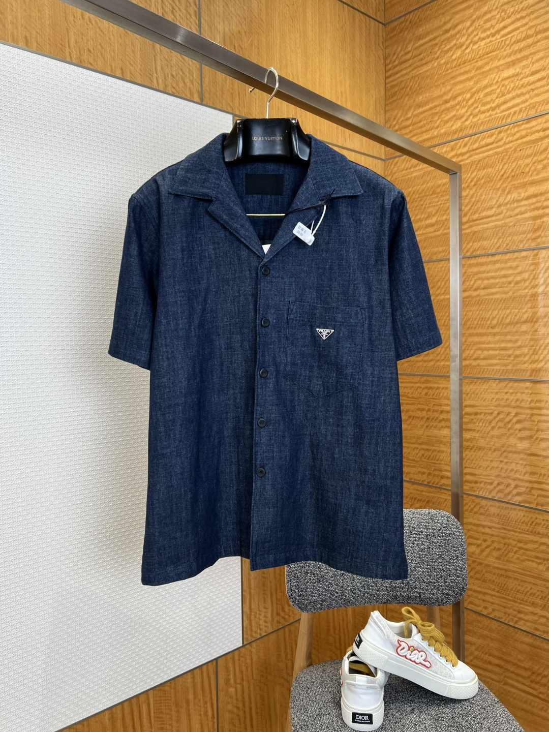NO:883743,P's Cuban collar washed denim short-sleeved shirt  It is made of long-staple cotton washed denim fabric, which has a natural retro indigo texture. It has a soft and waxy touch that weakens the stiffness of traditional denim. It has excellent breathability and anti-wrinkle drape properties. It is not easy to become hard and fade after repeated wear and washing, taking into account the retro texture and daily skin-friendly comfort. The neckline is cut with classic Cuban lapels and is hand-locked to prevent deformation and curling. The open collar modifies the neck line, eliminating tight constraints and allowing for casual relaxation.  The collar balances the neatness of formal wear and the casual and lazy temperament; the placket uses matte natural horn buttons of the same color, the button spacing is regularly arranged, and the hand-stitched buttonholes are strong and wear-resistant. The body adopts a slightly loose shoulder cut, side seam slits + curved hem double-needle close-coated seams, the routing is smooth and neat, the short-sleeved cuffs are neatly trimmed, and it is refreshing and smart to wear alone., Prada - Clothing, prada, shirts, T-shirt,19860909P家古巴领水洗牛仔短袖衬衫 采用长绒棉水洗牛仔面料,布面呈现自然复古靛蓝肌理,触感软糯弱化传统牛仔硬挺感,兼具出色透气度与抗皱垂坠属性,多次穿着洗涤不易发硬掉色,兼顾复古质感与日常亲肤舒适度；领口采用经典古巴翻领剪裁,手工锁边定型不易变形翻翘,开阔领型修饰脖颈线条,免去紧绷束缚,随性松弛的领型平衡正装利落与休闲慵懒气质；门襟选用同色系哑光天然牛角纽扣,扣距排布规整,手工锁缝扣眼牢固耐磨,衣身采用微宽松落肩剪裁,侧缝开衩+弧形下摆双针密拷锁边,走线平整工整,短袖袖口收边利落,单穿清爽干练.,普拉达-服装,prada,shirts,T-shirt,,Women's clothing