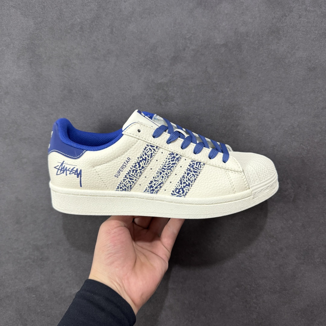 【定制版】Stussy x Adidas Original Superstar 斯图西 x 阿迪达斯 低帮联名米白蓝 贝壳头防滑耐磨轻便板鞋 鞋身整体采用米白色皮革打造，搭配经典米白贝壳头，鞋身两侧经典锯齿三条杠Logo采用蓝色点缀，侧身点缀蓝色Superstar字样，鞋舌上以蓝色Stussy及Adidas字样呈现，瞬间提升鞋子的时尚程度，后跟装饰片辅以蓝色皮革制作并带有白色Adidas字样及三叶草LLogo，后跟印有Stussy字样，彰显联名身份，最后以米白色中底搭配同色橡胶外底完善整体设计收尾。 货号：XG0009 尺码：36-45-选品中心
