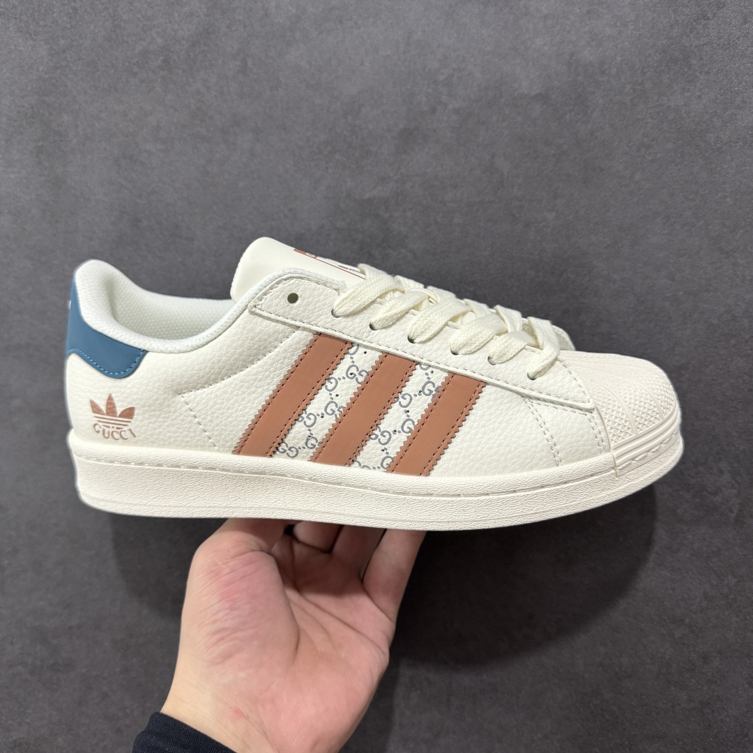 【定制版】Gucci x Adidas Original Superstar 古驰古奇 x 阿迪达斯 低帮 联名白棕蓝 贝壳头防滑耐磨轻便板鞋 鞋身整体采用米白色皮革打造，搭配经典米白贝壳头，鞋身两侧经典锯齿三条杠Logo采用棕色3M反光材质点缀，侧身点缀蓝色Superstar字样，鞋舌上以棕色Adidas字样及三叶草Logo呈现，瞬间提升鞋子的时尚程度，后跟装饰片辅以蓝色3M反光材质制作并带有白色Adidas字样及三叶草LLogo，后跟印有Gucci字样，彰显联名身份，最后以米白色中底搭配同色橡胶外底完善整体设计收尾。 货号：SD6817 尺码：36-45半-选品中心