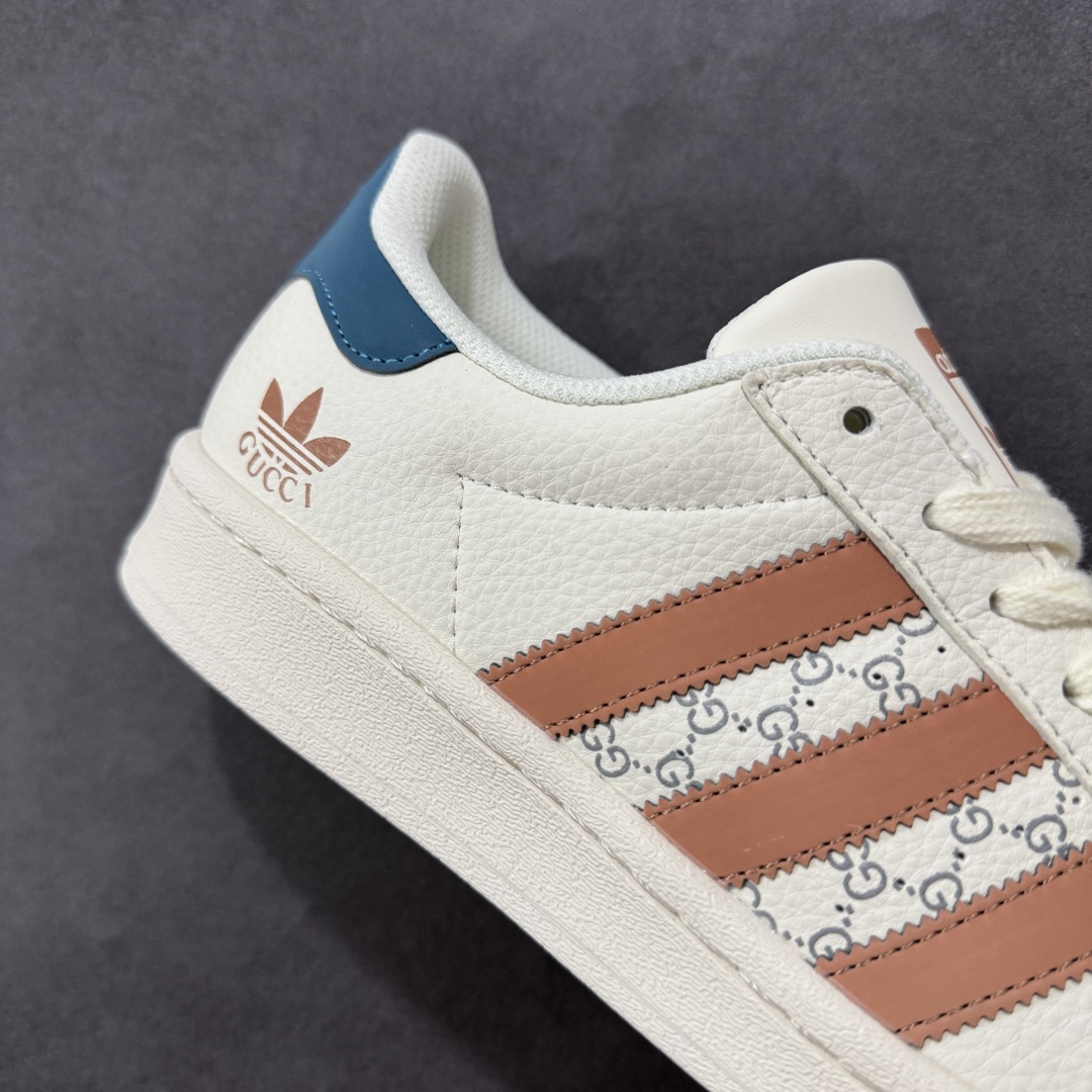 图片[6]-【定制版】Gucci x Adidas Original Superstar 古驰古奇 x 阿迪达斯 低帮 联名白棕蓝 贝壳头防滑耐磨轻便板鞋 鞋身整体采用米白色皮革打造，搭配经典米白贝壳头，鞋身两侧经典锯齿三条杠Logo采用棕色3M反光材质点缀，侧身点缀蓝色Superstar字样，鞋舌上以棕色Adidas字样及三叶草Logo呈现，瞬间提升鞋子的时尚程度，后跟装饰片辅以蓝色3M反光材质制作并带有白色Adidas字样及三叶草LLogo，后跟印有Gucci字样，彰显联名身份，最后以米白色中底搭配同色橡胶外底完善整体设计收尾。 货号：SD6817 尺码：36-45半-选品中心
