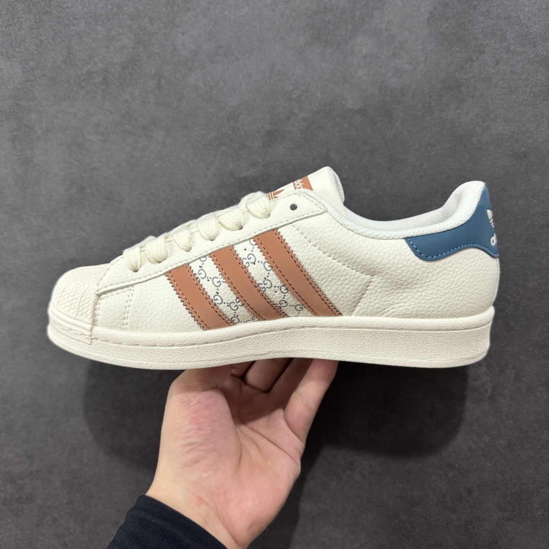 图片[2]-【定制版】Gucci x Adidas Original Superstar 古驰古奇 x 阿迪达斯 低帮 联名白棕蓝 贝壳头防滑耐磨轻便板鞋 鞋身整体采用米白色皮革打造，搭配经典米白贝壳头，鞋身两侧经典锯齿三条杠Logo采用棕色3M反光材质点缀，侧身点缀蓝色Superstar字样，鞋舌上以棕色Adidas字样及三叶草Logo呈现，瞬间提升鞋子的时尚程度，后跟装饰片辅以蓝色3M反光材质制作并带有白色Adidas字样及三叶草LLogo，后跟印有Gucci字样，彰显联名身份，最后以米白色中底搭配同色橡胶外底完善整体设计收尾。 货号：SD6817 尺码：36-45半-选品中心