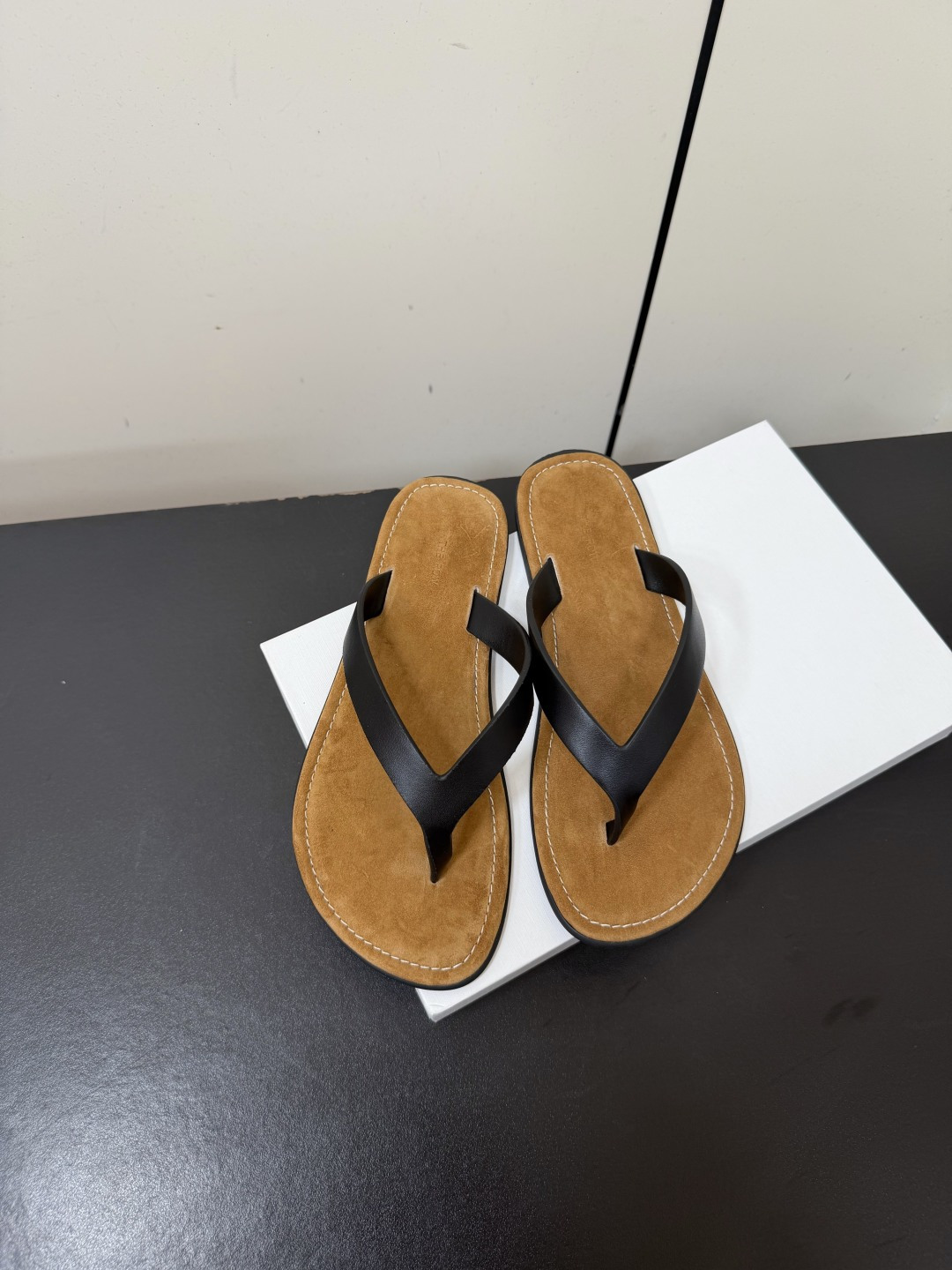 NO:902220,TheRow｜Minimalist flat-soled flip-flops, extremely simple 'no logo aesthetics', the shoe body does not have any unnecessary decoration, and is only presented with clean lines. It is a typical quiet luxury style, with a low-key sense of luxury. It comes in three basic colors of dark brown, pure black, and off-white, suitable for all summer wear scenarios.  The footbed is made of suede, which is soft to the touch and can reduce friction when walking; the toe strap is made of smooth leather, taking into account both texture and durability. The topstitching process on the edge of the shoe is a highlight of the details, making the overall silhouette cleaner and improving the sophistication of the shoe. size 35-41 (40.41 customized, non-refundable), split-toe shoes, chamois leather19860909TheRow｜极简平底夹趾人字拖 极致简约的“无logo美学” 鞋身没有任何多余装饰,仅以干净的线条呈现,是典型的安静奢华风格,自带低调高级感. 深棕、纯黑、米白三种基础配色,适配所有夏日穿搭场景. 鞋床采用麂皮材质,触感柔软,能减少走路时的摩擦感；夹趾带为光滑的皮革质感,兼顾质感与耐用性.鞋边的明线工艺是细节亮点,让整体轮廓更利落,也提升了鞋型的精致度. size35-41（40.41定制不退换）,分趾鞋,chamois leather,Women's Shoes