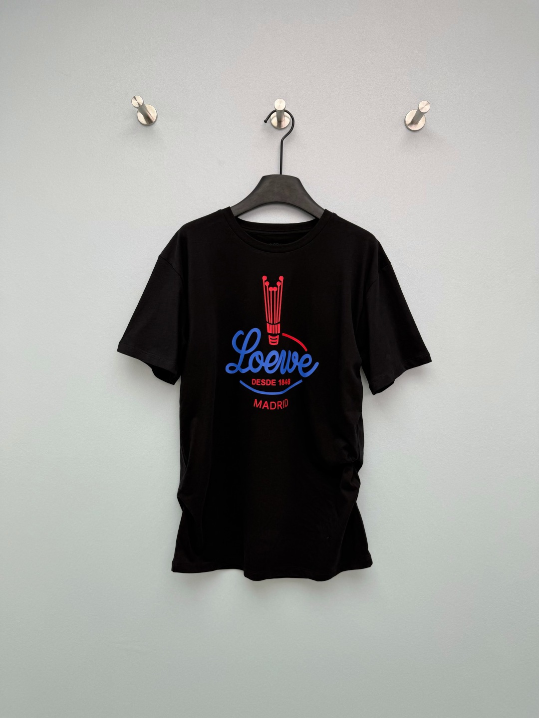 NO:776774,Loew*26 new retro American printed short-sleeved T-shirt. Multiple ways to wear it. Can be worn in a loose regular fit. Contains drawstring buttons that can be buttoned to instantly change into pleated designs on both sides. The red and blue badge print on the chest really gets more and more interesting the more you look at it. The candlestick logo + the handwritten brand name, the details are full of retro accents, 'DESDE'  1846' directly brings out the brand's sense of history. The pure cotton fabric is extremely comfortable, and the loose fit is friendly to all body types. Paired with jeans, it is an American street style. Paired with a skirt, it instantly transforms into a retro lady. You can't go wrong with black and white with your eyes closed!  2 colors and 3 codes SML, Loewe-clothing, loewe, loewe, skirts, jeans, T-shirt, tees, t-shirt,19860909Loew*26新款复古美式印花短袖T恤 多种穿搭方式 可宽松常规版型 内含抽绳纽扣可系扣秒变两侧褶皱设计 胸前的红蓝徽章印花真的越看越有味道,烛台标识+手写体品牌名,细节里全是复古腔调,“DESDE 1846”直接把品牌历史感拉满.纯棉面料巨舒服,宽松版型对各种身材都友好,搭配牛仔裤是美式街头风,配半裙又秒变复古大小姐,黑白两色闭眼入都不会错！2色3码SML,罗意威-服装,loewe,loewe,skirts,jeans,T-shirt,tees，t-shirt,,Women's clothing