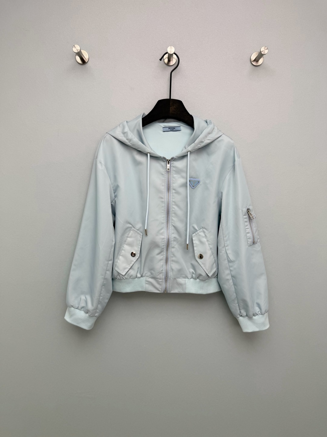 NO:776539,PRAD*26 new triangle logo hooded nylon flight jacket  It is made of high-density waterproof nylon fabric, which is smooth to the touch and has good windproof and anti-wrinkle properties. The upper body is light and has no weight-bearing feeling. The chest, arm pockets and zipper pullers are all equipped with the same color triangular metal LOGO, which has a full texture and instantly enhances the luxury of the item. It is P  The core identification point of home style. The black model is a timeless classic, cool and slim, suitable for all ages; the ice blue model is very 'golden', fresh and age-reducing, the fabric is crisp and not easy to wrinkle, easy to take care of, and has a good drape, which can well support the pattern!  The flight jacket is my destiny!  2 colors and 3 codes SML,Prada-clothing,prada,prada,jackets & coats,jackets & coats,hats,19860909PRAD*26新款三角标连帽尼龙飞行夹克外套 采用高密防水尼龙面料,触感顺滑且具备良好的防风抗皱性能,上身轻盈无负重感.胸前、臂袋及拉链头均配备同色系三角金属LOGO,质感饱满,瞬间提升单品奢华感,是P家风格的核心识别点.黑色款是永不过时的经典,酷飒显瘦,适配全年龄段；冰蓝款则极具“千金感”,清新减龄,面料挺括不易皱,方便打理,且垂坠感好,能很好地支撑版型！本命飞行夹克了！2色3码SML,普拉达-服装,prada,prada,jackets & coats,jackets & coats,hats,,Women's clothing