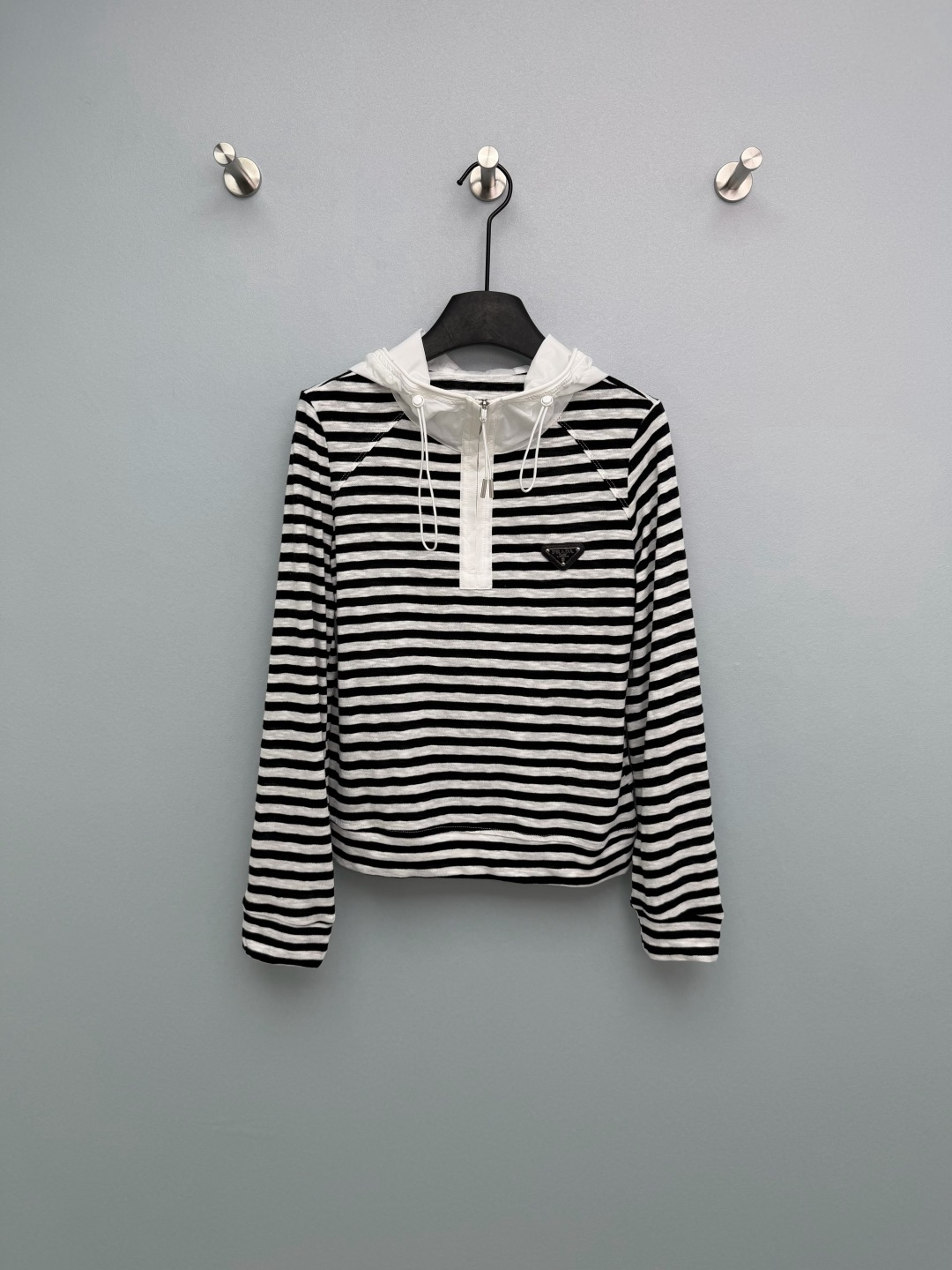 NO:777972,Prad*26 new triangular logo half-zip hooded long-sleeved top. Half-zip opening and closing design, the collar height can be adjusted freely to create different styles. The zipper texture is smooth and the opening and closing is smooth. The hat body is made of contrasting nylon fabric, which is stiff and stylish, not easy to collapse, and forms a layered contrast with the body. The brand's classic black triangle metal logo is inlaid on the left chest, adjustable drawstring + metal rope buckle, white is clean and high-end, stripes are classic and retro, both colors are magical!  ps The overall white color will be a little larger than the stripes~ 2 colors and 3 sizes SML, Prada-clothing, prada, prada, hats,19860909Prad*26新款三角标半拉链连帽长袖上衣 半拉链开合设计,可自由调节领口高度,打造不同穿搭风格,拉链质感顺滑,开合流畅.帽身采用撞色尼龙面料,挺括有型,不易软塌,与衣身形成层次对比,设计感拉满.左胸处镶嵌品牌经典黑色三角金属标, 可调节抽绳+金属绳扣,白色干净高级,条纹经典复古,两色都封神！ps白色整体会比条纹大一点~ 2色3码SML,普拉达-服装,prada,prada,hats,,Women's clothing