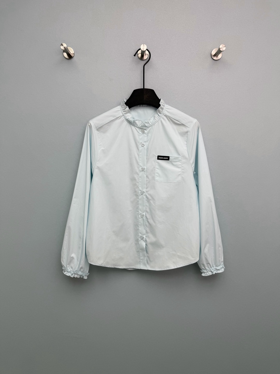 NO:777965,Miu Mi*26 new fungus stand-collar long-sleeved shirt. The collar and cuffs are double-layered with fungus stitching. The lines are neat, smart and sweet, which is the soul element of the sweet style. The left chest pocket is inlaid with the brand's classic black background and white text woven label, which is highly recognizable and full of light luxury. The details are exquisite. The slightly loose version is not flattering, and the flesh is directly hidden. The white is clean and refreshing, and the light blue is gentle and white, welding the girly feeling on the body!  2 colors and 3 codes SML, Miumiu-clothing, miumiu, shirts,19860909Miu Mi*26新款木耳边立领长袖衬衫 领口、袖口双层木耳边拼接,走线工整,灵动甜美,是甜系风格的灵魂元素.左胸口袋处镶嵌品牌经典黑底白字织唛,辨识度拉满,轻奢感十足,细节精致.微宽松版型不挑身材,拜拜肉直接藏住 白色干净清爽,浅蓝温柔显白,把少女感焊在身上！2色3码SML,缪缪-服装,miumiu,shirts,,Women's clothing