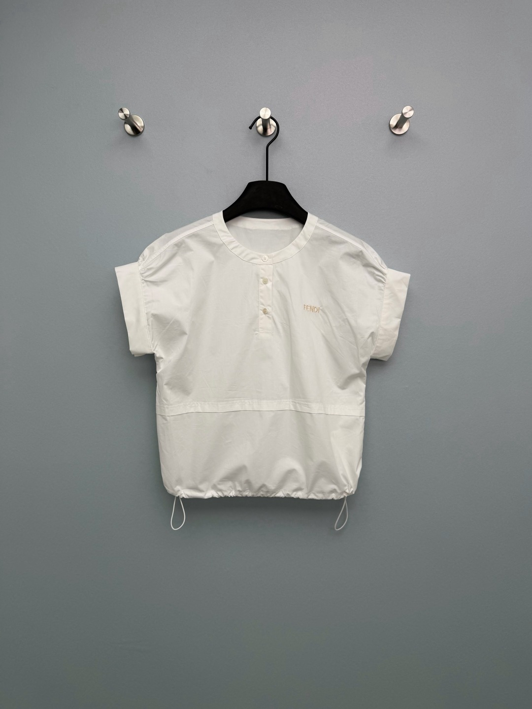 NO:778356,FEND*26 new logo embroidered drawstring round neck short-sleeved shirt. The letter embroidery on the left chest is amazing!  The light gold thread is low-key and recognizable. It is not the kind of exaggerated big logo. It has a light and luxurious feel. Dropped shoulder sleeves + loose fit, which is too friendly for pear-shaped and shoulder-shaped figures. Pull the drawstring at the hem, and it will become shorter and reveal the waist in seconds. The hot girl feeling will come out directly. Without pulling the drawstring, it will give you a lazy and relaxed feeling, suitable for commuting. The crisp fabric does not stick to the flesh at all, and is breathable and comfortable in summer.  One piece covers all the outfits in spring and summer. You can close your eyes without stepping on thunder. This white shirt is really the ivy in the wardrobe. Single color size 3 SML, Fendi-clothing, fendi, fendi, shirts, T-shirt,19860909FEND*26新款logo刺绣抽绳圆领短袖衬衫 左胸的字母刺绣太绝了！浅金走线低调又有辨识度,不是那种浮夸的大logo,轻奢感直接拉满 落肩袖+宽松版型,对梨形、溜肩身材太友好了 下摆抽绳一拉,秒变短款露腰,辣妹感直接出来 不拉抽绳就是慵懒松弛感,通勤穿得体又大方 挺括的面料完全不贴肉,夏天穿透气又舒服 一件承包春夏所有穿搭,闭眼入不踩雷 这件白衬衫真的是衣柜里的常青藤了 单色3码SML,芬迪-服装,fendi,fendi,shirts,T-shirt,,Women's clothing