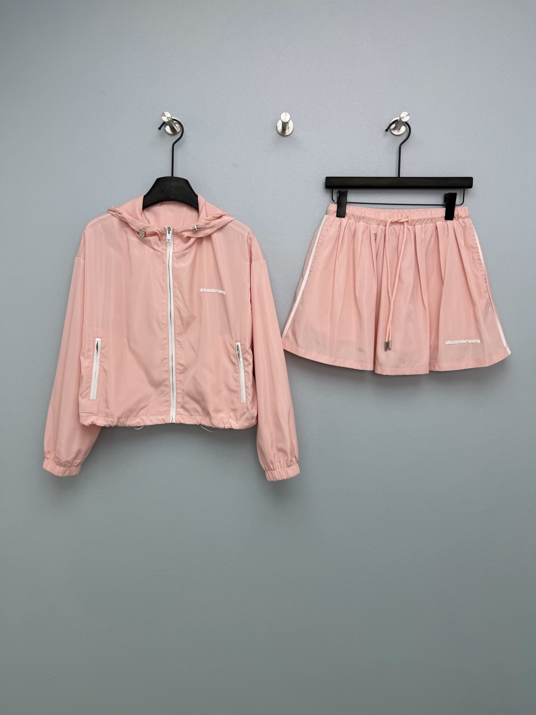 NO:780344,Alexander Wa*g26 new hooded sun protection jacket + drawstring skirt two-piece suit. The jacket + skirt are complete sets, no need to worry about matching, one set can be used for spring and summer, saving time and pictures. The short version of the jacket raises the waistline and transforms into a 37-point figure in seconds; the hooded design + drawstring adjustment, full of casual feeling; double side zipper pockets, practical and beautiful  The A-line drawstring skirt has an elastic waist and a drawstring design, which is not flattering to the figure and is friendly to the waist and abdominal muscles; the A-line large skirt covers the flesh and looks slimming, and the side white edges are designed with contrasting colors, giving it a sweet and cool feel. Both the jacket and skirt are printed with the Alex brand letter logo, which shows the brand texture in a low-key manner and full of details.  It is made of breathable and sun-proof nylon fabric, which is light and breathable, sun-proof and anti-wrinkle. It is refreshing and not sweaty when worn in spring and summer. It has a mesh lining inside, which is breathable and not stuffy. There are two fairy colors of peach pink/navy blue, which can be used by both sweet girls and cool girls!  2 colors and 3 codes SML, alexander wang-clothing, alexander wang,skirts,jackets & coats,hats,19860909Alexander Wa*g26新款连帽防晒外套+抽绳短裙两件套套装 外套+短裙成套搭配,不用费心搭配,一套搞定春夏穿搭,省时又出片 外套短款版型拉高腰线,秒变三七分身材；连帽设计+抽绳调节,休闲感拉满；双侧拉链口袋,实用又美观 A字抽绳短裙松紧腰+抽绳设计,不挑身材,对腰腹肉肉友好；A字大裙摆遮肉显瘦,侧边白边撞色设计,甜酷感拉满 外套、短裙均印有alex品牌字母标,低调彰显品牌质感,细节感拉满 采用透气防晒的尼龙面料,轻薄透气,防晒抗皱,春夏穿着清爽不闷汗,内搭网眼衬里,透气不闷.蜜桃粉/藏青两种神仙配色,甜妹/酷姐都能驾驭！2色3码SML,亚历山大王-服装,alexander wang,skirts,jackets & coats,hats,,Women's clothing